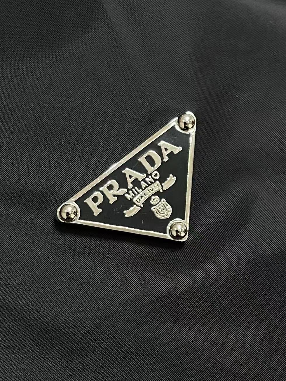 Prada 饰标翻领小外套，精选高密织造尼龙面料，纤维肌理紧实饱满，整体质地轻盈轻薄，上身零负重。面料经