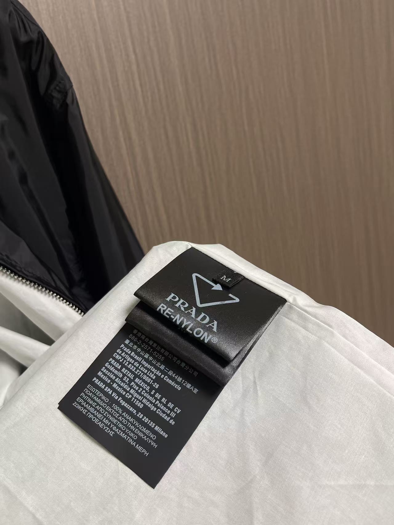 Prada 饰标翻领小外套，精选高密织造尼龙面料，纤维肌理紧实饱满，整体质地轻盈轻薄，上身零负重。面料经