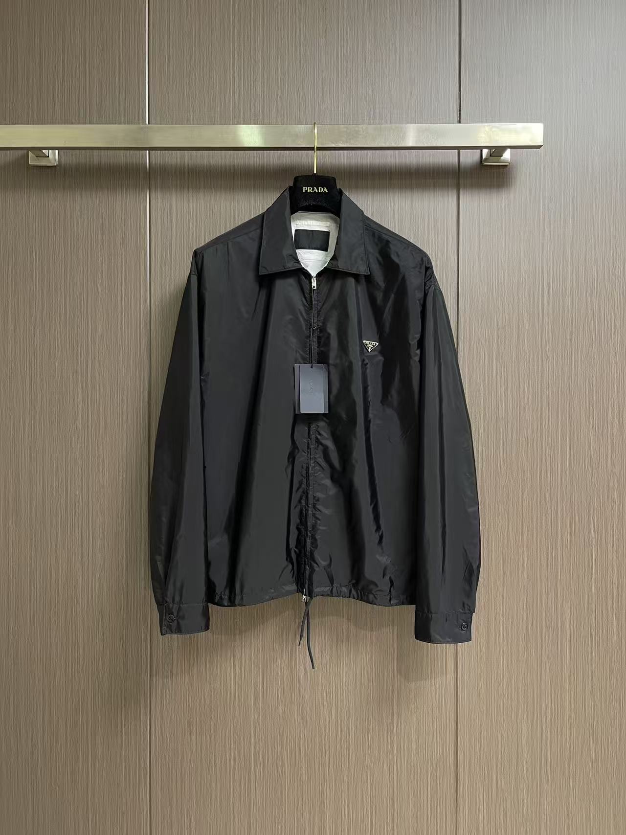 Prada 饰标翻领小外套，精选高密织造尼龙面料，纤维肌理紧实饱满，整体质地轻盈轻薄，上身零负重。面料经