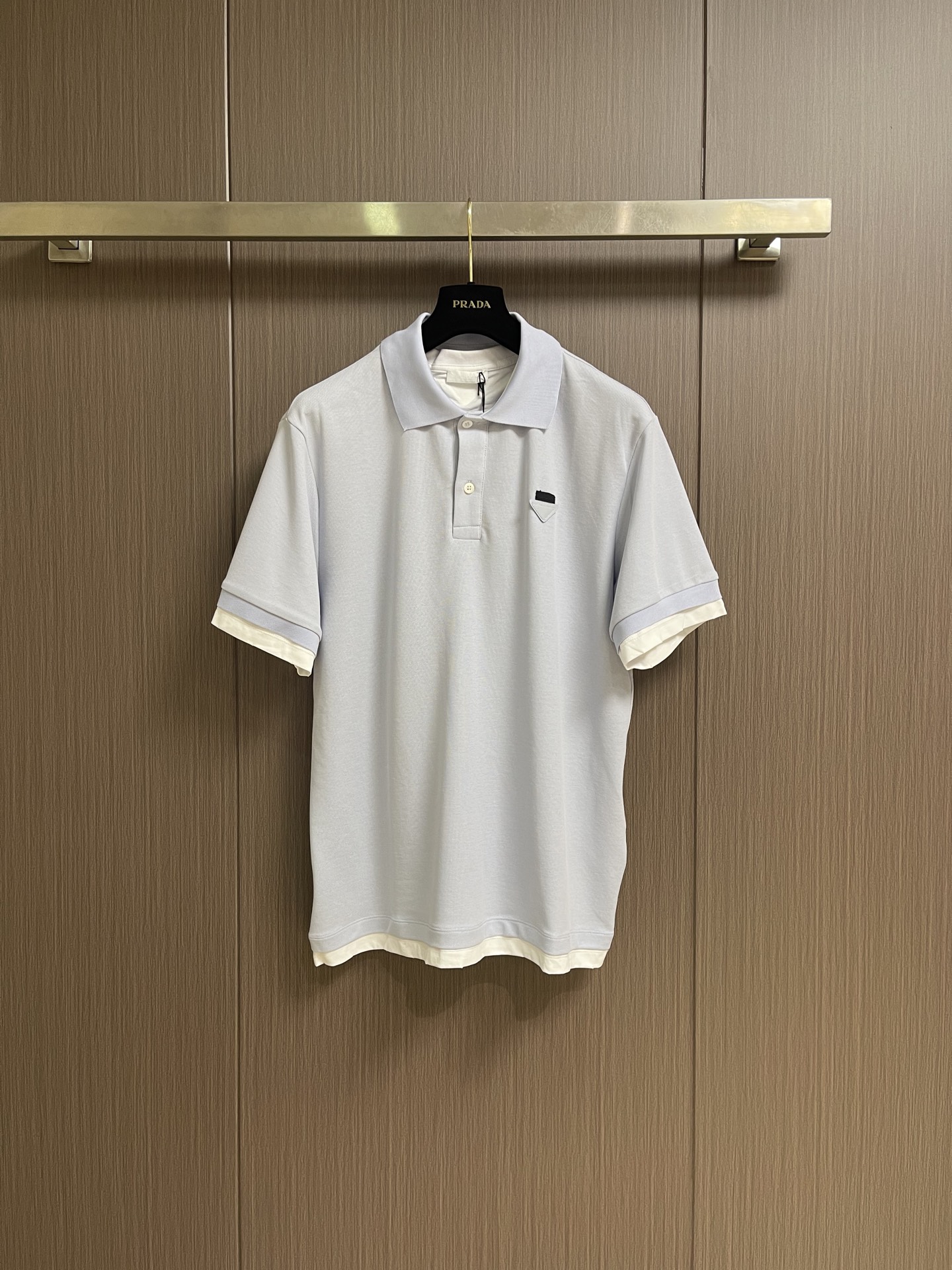 NO:903982,Prada The POLO shirt with contrasting fabric triangle logo is made of pique fabric woven from cotton fiber. The cotton fiber gives the fabric the characteristics of moisture absorption, breathability, and skin-friendliness. The surface of the pique structure has uneven holes, shaped like a honeycomb, which promotes air circulation and has excellent heat dissipation efficiency. Because the elasticity of cotton yarn is enhanced after pique weaving, it can still rebound after repeated stretching. The rib knitted neckline is knitted with a double needle bed, so that the loops are alternately formed on the front and back sides to form a The 1*1 rib with longitudinal concave and convex patterns. The elastic structure makes the neckline naturally fit the neck to avoid a sense of restraint. The double-layer sewing process links the body, which significantly reduces the probability of the neckline expanding into a 'ruffle' and collapsing, and maintains its initial shape for a long time. By actively intervening in the shrinkage potential of cotton fibers, the fabric is able to cross from changeable to stable, improving dimensional stability while not easily deformed and wrinkled. Sizes S-XL Size S, shoulder width 47, bust 106, Length 71.5, size M, shoulder width 48, bust 110, length 73, L size, shoulder width 49, bust 114, length 74.5, XL, shoulder width 50, bust 118, length 76,, prada,19860909Prada 饰撞色织物三角标POLO衫,选用棉纤维编织而成的珠地布.棉纤维赋予面料吸湿透气,亲肤等特点.珠地结构表面呈现凹凸疏孔,形似蜂巢,促进空气循环,散热效率优良.因棉纱经珠地编织后弹性增强,反复拉伸仍可回弹.罗纹针织领口使用双针床编织,使线圈在正反面交替成圈,形成纵向凹凸纹路的1*1罗纹.弹性结构使领口自然贴合颈部,避免束缚感,加之双层缝纫工艺链接衣身,显著降低领口外扩成“荷叶边”的概率与塌陷,保持长久初始形态.通过主动干预棉纤维收缩潜能,实现了面料从易变到稳定的跨越,提升了尺寸稳定性,同时不易变形,褶皱.尺码S-XL  S码 肩宽47 胸围106衣长71.5 M码肩宽48 胸围110 衣长73 L码 肩宽49 胸围114 衣长74.5 XL码 肩宽50 胸围118 衣长76,,prada,,Men's clothing