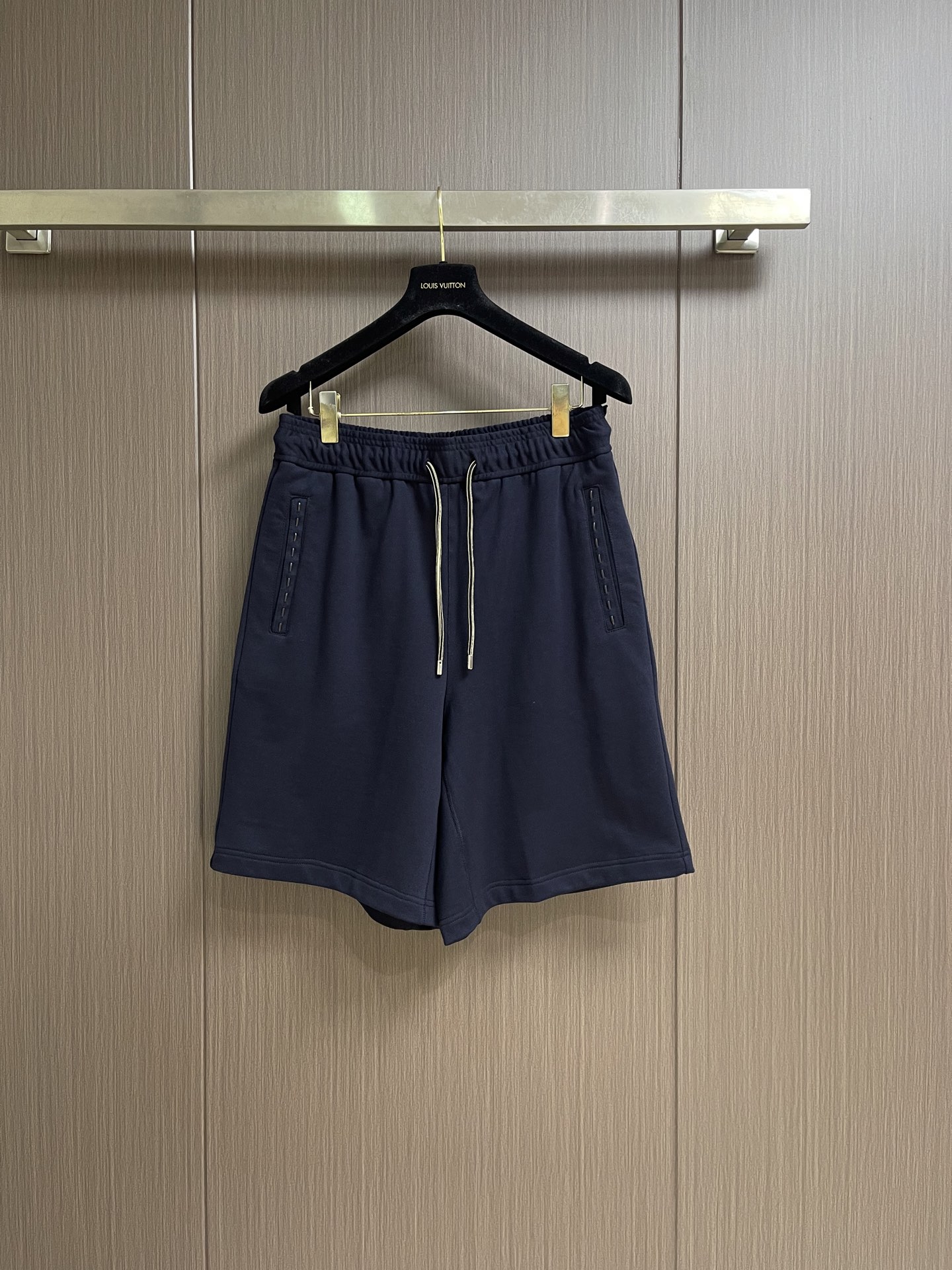 NO:903922,FENDI  Letter patch cotton shorts are made of cotton woven through fine plain knitting. The yarns are intertwined tightly and evenly. The fabric texture is clear and regular. The fabric has excellent resilience and toughness. It is not easy to produce stubborn wrinkles after being rubbed and bent. It can maintain a flat shape even when sitting or walking for a long time. The natural cotton base has a soft skin-friendly touch, and there is no itch when worn next to the skin.  The pore structure is breathable and moisture-absorbing, quickly dissipating moisture on the body surface, and it is not easy to stick to the body and sweat in hot and humid environments for a long time. The fabric density is moderate, taking into account softness and support, and will not be too soft and close to the body. The drape is natural and stylish. The sides of the bag mouth are decorated with equidistant and regular leather strips, and the flexible leather strips are accurately embedded in the preset wiring holes and arranged at even intervals.  Cloth, sewn lines are firmly locked in place, and will not easily shift and loosen after long-term use. At the same time, the striped lines are threaded to reinforce the fabric structure at the edge of the bag mouth, which disperses the tensile stress of daily items and effectively prevents the bag mouth from deforming. Its touch is warm and moist and does not irritate the skin. The lines are smooth and fit the fabric, which has both decorative beauty and structural practicality. The back pocket is sewn with neat diamond-shaped patch pockets.  Craftsmanship, double threads are evenly lockstitched around the bag mouth, and the stitch length is fine and uniform, firmly fixing the bag body and trousers body fabric, and the structure is stable and durable. The custom embossed leather label is inlaid in the center of the bag body, the letter pattern is clear and three-dimensional, the texture is delicate, the edges are precisely stitched and are not easy to peel off, taking into account practicality and detailed texture, the overall workmanship is exquisite and durable. Sizes S-XL  46-52 46 yards, waist circumference 76, sitting circumference 108, trouser length 53, 48 yards, waist circumference 80, sitting circumference 112, trouser length 54, 50 yards, waist circumference 84, sitting circumference 116, trouser length 55, 52 yards, waist circumference 88, sitting circumference 120, trouser length 56,,fendi,shorts,19860909FENDI 字母贴饰棉质短裤,采用棉通过细密平纹针织织造而成,纱线交织紧实均匀,织物纹理清晰规整,面料回弹韧性出色,揉搓弯折后不易产生顽固褶皱,日常久坐、走动也能保持平整版型.天然棉基底自带柔和亲肤触感,贴肤穿着无刺痒感,孔隙结构透气吸湿,快速疏导体表湿气,久坐闷热环境也不易黏身闷汗.面料密度适中,兼顾柔软度与支撑性,不会过分软塌贴身,垂坠自然有型.袋口侧边设有等距规整皮质穿条装饰工艺,柔韧皮质细条精准嵌入预设走线孔位,间距均匀排布,缝制走线牢牢锁固点位,久用不易移位松脱.同时穿条走线加固袋口边缘织物结构,分散日常掏取物件的拉扯应力,有效防止袋口变形,其触感温润不硌皮肤,走线平整贴合面料,装饰美感与结构实用性兼备.后袋采用工整菱形贴袋缝制工艺,双线均匀锁缝袋口四周,针距细密统一,牢牢固定袋体与裤身面料,结构稳固耐用.袋体正中镶嵌定制压印皮标,字母纹路清晰立体,质感细腻,边缘精密车线不易开胶脱落,兼顾实用性与细节质感,整体做工精致耐看.尺码S-XL 46-52  46码 腰围76坐围108 裤长53  48码 腰围80坐围112裤长54  50码 腰围84坐围116裤长55  52码 腰围88坐围120裤长56,,fendi,shorts,,Men's clothing