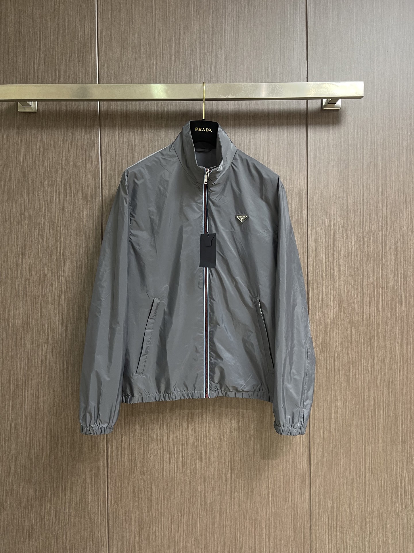 NO:911678,Prada  Zipper-trimmed stand-up collar jacket, made of selected high-density woven nylon fabric, with firm and full fiber texture, light and thin overall texture, and zero weight on the upper body. After the fabric has been treated with water-repellent treatment, slight wet water will not easily adhere to it, and it also has excellent anti-fouling ability, making daily stains easy to wipe and clean. The fiber characteristics make the woven fabric tough.  Excellent, tear-resistant and anti-snagging, not prone to wrinkling and collapse when worn for a long time, and can maintain a neat and crisp silhouette even when worn for a long time, taking into account both beauty and practicality. It adopts an embedded double-layered edge zipper placket, the outside of the burgundy zipper teeth is covered with light blue webbing, and the outer layer is wrapped with gray fabric, and the zipper tape is fixed and routed with two fine topstitches.  Uniform and straight, the appearance is neat and layered. The custom-engraved metal puller drives the opening and closing. After the finished garment is finished, it is ironed at low temperature to smooth out the wrinkles and trim the threads. The left and right plackets are symmetrical and regular, and the hemming width is consistent, which not only improves the windproof sealing, but also combines durability and high-end texture. The hem and cuffs adopt a double-layer elastic gathering process to ensure smoothness.  The smooth nylon fabric is folded and overlocked with embedded elastic bands, and the double threads are evenly sewn and fixed. The stitch length is regular and fine, and the pleats are evenly arranged and natural. The elasticity is moderate, tightening to fit the body shape without tightening the skin, effectively blocking the intrusion of wind and rain, and improving the windproof and temperature locking effect. The overall wiring is straight and delicate, the fabric is comfortable and soft, and the color is consistent without color difference.  Can be matched with the same style to create a fashionable look, to suit various occasions, customized accessories, complete with three standards!  Sizes S-XL S size Shoulder width 51 Bust 118 Length 69 Medium Shoulder width 52 Bust 122 Length 70.5 L size Shoulder width 53 Bust 126 Length 72 XL Shoulder width 54 Bust 130 Length 73.5,,prada,jackets & coats,jackets & coats,19860909Prada 拉链饰边立领夹克外套,精选高密织造尼龙面料,纤维肌理紧实饱满,整体质地轻盈轻薄,上身零负重.面料经过防泼水处理之后,轻微湿水不易附着,同时具备优良抗污能力,日常污渍易擦拭清洗.纤维特性使织成的面料韧性出色,抗撕裂、防勾丝,久穿不易起皱塌陷,长久穿着也能维持利落挺括的廓形,兼顾美观与实用性.采用嵌入式双层包边拉链门襟,酒红色拉链齿外侧包覆浅蓝色织带,外层再用灰色衣料包裹拉链布带,两道精细明线固定,走线均匀笔直,外观整洁层次分明.定制刻标金属拉头带动开合,成衣之后进行低温整烫抚平褶皱、修剪线头,门襟左右对称规整,包边宽度一致,既提升防风密封性,又兼具耐用性与高级质感.下摆与袖口采用双层松紧收束工艺,光滑尼龙面料对折包缝内嵌松紧带,双线均匀车缝固定,针距规整细密,褶皱排布匀称自然.松紧弹力适中,收紧贴合身形又不紧绷勒肤,有效阻挡风雨灌入,提升防风锁温效果.整体走线平直细腻,面料舒适柔软,颜色一致无色差 能与同款搭配营造时尚造型,驾驭各种场合,定制辅料,三标齐全！尺码S-XL  S码 肩宽51 胸围118 衣长69 M码肩宽52 胸围122 衣长70.5 L码 肩宽53 胸围126 衣长72 XL码 肩宽54 胸围130 衣长73.5,,prada,jackets & coats,jackets & coats,,Men's clothing
