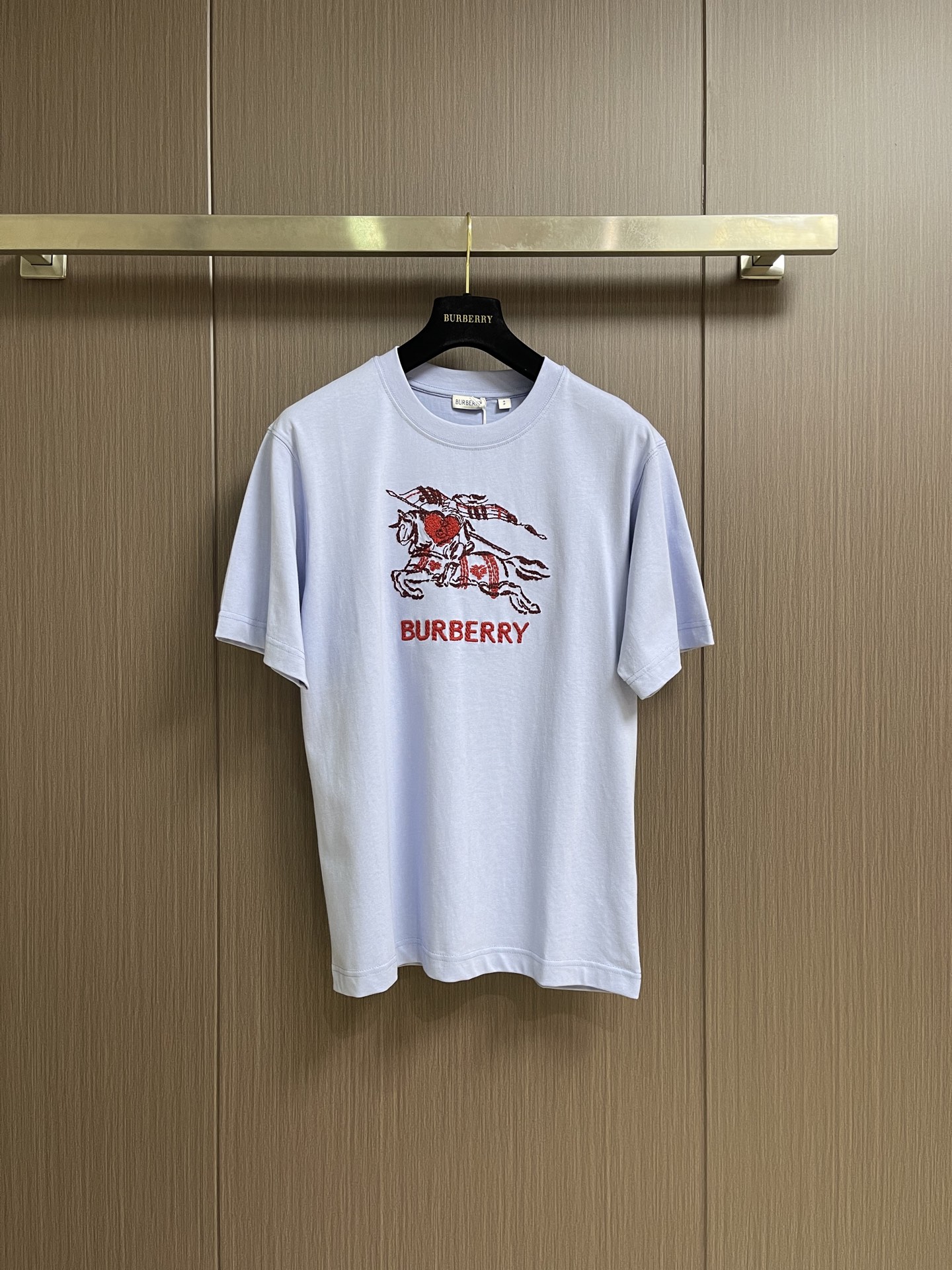 NO:911702,Burberry  The Love Shield War Horse round-neck short-sleeved T-shirt is made of 15-count special-spun compact cotton with a weight of 230g㎡; it is paired with 32-count high-weight 1x1 ribs for the neckline, with a weight of 349g㎡. The special-spun compact cotton uses compact spinning technology in the spinning process, which effectively reduces  The yarn hairiness is reduced, making the fabric structure denser, the surface smoother, and the pilling resistance better. The weight of the fabric is medium to heavy, ensuring that the T-shirt has good stiffness and drape, and is not easy to collapse and deform. Its high count and high weight characteristics ensure excellent elastic recovery of the collar.  Strength, thickness and resistance to deformation are the hallmarks of high-quality T-shirts. Multi-thread rice grain embroidery is an embroidery process characterized by short, dense granular stitches. The embroidery threads are arranged layer by layer in oval-shaped small units that approximate rice grains, and are interwoven and superimposed by multi-color, multi-strand threads  , forming a full and textured surface effect. Each stitch rises and falls independently, leaving a slight gap between stitches, making the embroidery surface show a natural roughness and three-dimensional layering similar to grain accumulation. The overall wiring is straight and delicate, the fabric is comfortable and soft, and the color is consistent without color difference.  Can be matched with the same style to create a fashionable look, to suit various occasions, customized accessories, complete with three standards!  Size XS-L19860909Burberry 爱心盾牌战马圆领短袖T恤,采用15支特纺紧密棉,克重为230g㎡；搭配32支高克重1x1罗纹用于领口,克重为349g㎡.特纺紧密棉在纺纱环节应用了紧密纺技术,有效减少了纱线毛羽,使得面料结构更密实、表面更光洁、抗起球性更佳.面料克重属于中等偏重磅,确保了T恤良好的挺括感和垂坠性,不易软塌变形.其高支高克重特性确保了领型极佳的弹性恢复力、厚实感和抗变形能力,是高品质T恤的标志.多线米粒绣是一种以短促、密集的颗粒状针迹为特征的刺绣工艺.绣线以近似米粒的椭圆形小单元层层排列,通过多色、多股线的交织叠加,形成饱满而富有肌理感的表面效果.每一针均独立起落,针迹之间留有细微间隙,使绣面呈现出类似谷物堆积的天然粗糙感与立体层次.整体走线平直细腻,面料舒适柔软,颜色一致无色差 能与同款搭配营造时尚造型,驾驭各种场合,定制辅料,三标齐全！尺码XS-L XS码胸围103肩宽47衣长71 S码 胸围107肩宽48.5衣长73 M码胸围111 肩宽50衣长75 L码 胸围115肩宽51.5 衣长77,,burberry,T-shirt,tees，t-shirt,,Men's clothing