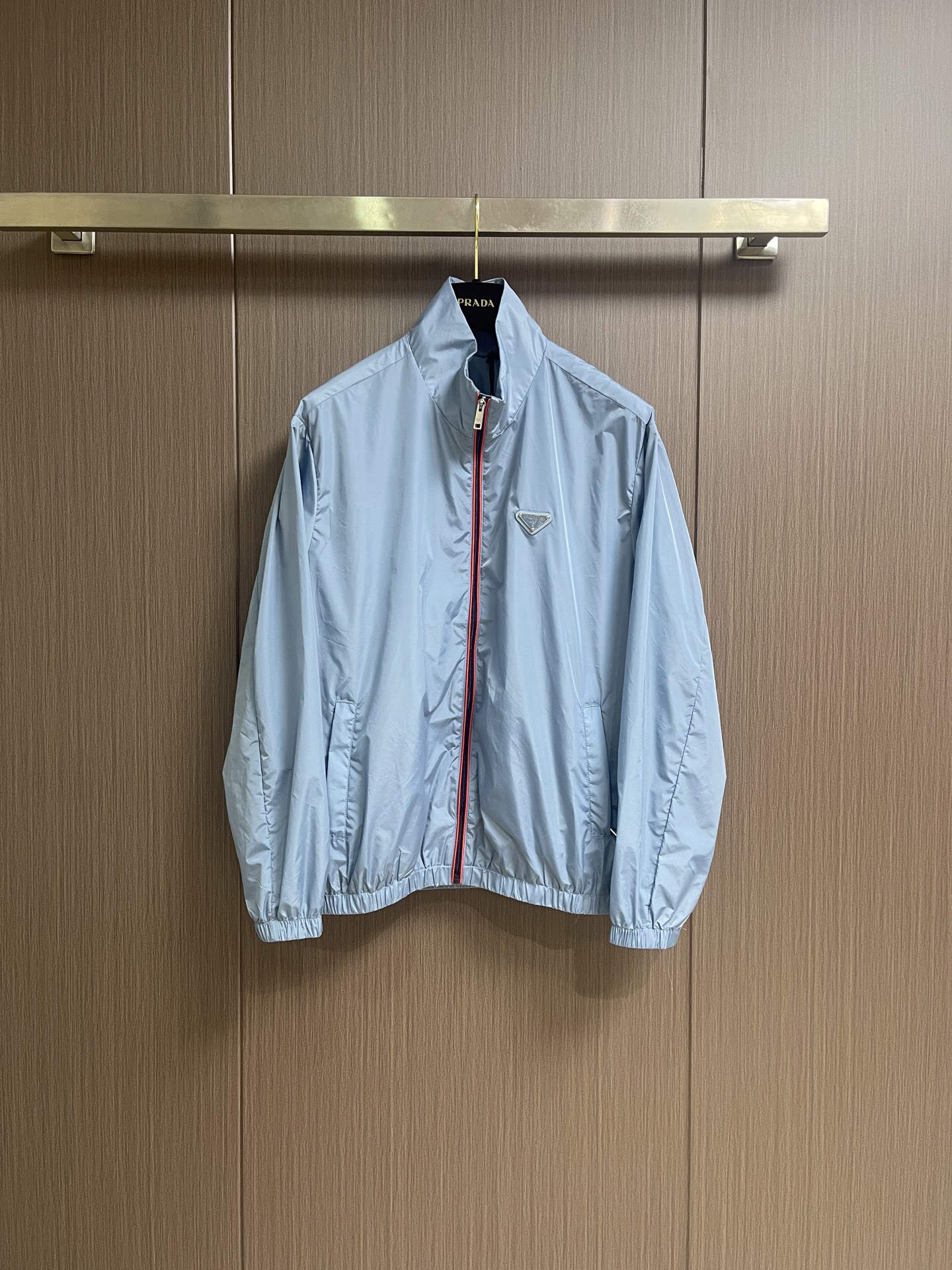 NO:911694,Prada  Zipper-trimmed stand-up collar jacket, made of selected high-density woven nylon fabric, with firm and full fiber texture, light and thin overall texture, and zero weight on the upper body. After the fabric has been treated with water-repellent treatment, slight wet water will not easily adhere to it, and it also has excellent anti-fouling ability, making daily stains easy to wipe and clean. The fiber characteristics make the woven fabric tough.  Excellent, tear-resistant and anti-snagging, not prone to wrinkling and collapse when worn for a long time, and can maintain a neat and crisp silhouette even when worn for a long time, taking into account both beauty and practicality. It adopts an embedded double-layered edge zipper placket, the outside of the burgundy zipper teeth is covered with light blue webbing, and the outer layer is wrapped with gray fabric, and the zipper tape is fixed and routed with two fine topstitches.  Uniform and straight, the appearance is neat and layered. The custom-engraved metal puller drives the opening and closing. After the finished garment is finished, it is ironed at low temperature to smooth out the wrinkles and trim the threads. The left and right plackets are symmetrical and regular, and the hemming width is consistent, which not only improves the windproof sealing, but also combines durability and high-end texture. The hem and cuffs adopt a double-layer elastic gathering process to ensure smoothness.  The smooth nylon fabric is folded and overlocked with embedded elastic bands, and the double threads are evenly sewn and fixed. The stitch length is regular and fine, and the pleats are evenly arranged and natural. The elasticity is moderate, tightening to fit the body shape without tightening the skin, effectively blocking the intrusion of wind and rain, and improving the windproof and temperature locking effect. The overall wiring is straight and delicate, the fabric is comfortable and soft, and the color is consistent without color difference.  Can be matched with the same style to create a fashionable look, to suit various occasions, customized accessories, complete with three standards!  Size S-XL S size bust 119 shoulder width 52 length 67 M size bust 123 shoulder width 53 length 68.5 L size bust 127 shoulder width 54 length 70 XL size bust 131 shoulder width 55 length 72.5,,prada,jackets & coats,jackets & coats,19860909Prada 拉链饰边立领夹克外套,精选高密织造尼龙面料,纤维肌理紧实饱满,整体质地轻盈轻薄,上身零负重.面料经过防泼水处理之后,轻微湿水不易附着,同时具备优良抗污能力,日常污渍易擦拭清洗.纤维特性使织成的面料韧性出色,抗撕裂、防勾丝,久穿不易起皱塌陷,长久穿着也能维持利落挺括的廓形,兼顾美观与实用性.采用嵌入式双层包边拉链门襟,酒红色拉链齿外侧包覆浅蓝色织带,外层再用灰色衣料包裹拉链布带,两道精细明线固定,走线均匀笔直,外观整洁层次分明.定制刻标金属拉头带动开合,成衣之后进行低温整烫抚平褶皱、修剪线头,门襟左右对称规整,包边宽度一致,既提升防风密封性,又兼具耐用性与高级质感.下摆与袖口采用双层松紧收束工艺,光滑尼龙面料对折包缝内嵌松紧带,双线均匀车缝固定,针距规整细密,褶皱排布匀称自然.松紧弹力适中,收紧贴合身形又不紧绷勒肤,有效阻挡风雨灌入,提升防风锁温效果.整体走线平直细腻,面料舒适柔软,颜色一致无色差 能与同款搭配营造时尚造型,驾驭各种场合,定制辅料,三标齐全！尺码S-XL S码胸围119 肩宽52衣长67 M码 胸围123 肩宽53衣长68.5 L码胸围127 肩宽54衣长70 XL码 胸围131 肩宽55衣长72.5,,prada,jackets & coats,jackets & coats,,Men's clothing