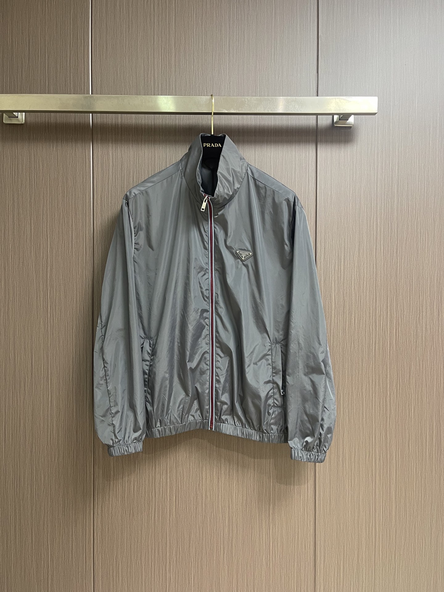 NO:911698,Prada  Zipper-trimmed stand-up collar jacket, made of selected high-density woven nylon fabric, with firm and full fiber texture, light and thin overall texture, and zero weight on the upper body. After the fabric has been treated with water-repellent treatment, slight wet water will not easily adhere to it, and it also has excellent anti-fouling ability, making daily stains easy to wipe and clean. The fiber characteristics make the woven fabric tough.  Excellent, tear-resistant and anti-snagging, not prone to wrinkling and collapse when worn for a long time, and can maintain a neat and crisp silhouette even when worn for a long time, taking into account both beauty and practicality. It adopts an embedded double-layered edge zipper placket, the outside of the burgundy zipper teeth is covered with light blue webbing, and the outer layer is wrapped with gray fabric, and the zipper tape is fixed and routed with two fine topstitches.  Uniform and straight, the appearance is neat and layered. The custom-engraved metal puller drives the opening and closing. After the finished garment is finished, it is ironed at low temperature to smooth out the wrinkles and trim the threads. The left and right plackets are symmetrical and regular, and the hemming width is consistent, which not only improves the windproof sealing, but also combines durability and high-end texture. The hem and cuffs adopt a double-layer elastic gathering process to ensure smoothness.  The smooth nylon fabric is folded and overlocked with embedded elastic bands, and the double threads are evenly sewn and fixed. The stitch length is regular and fine, and the pleats are evenly arranged and natural. The elasticity is moderate, tightening to fit the body shape without tightening the skin, effectively blocking the intrusion of wind and rain, and improving the windproof and temperature locking effect. The overall wiring is straight and delicate, the fabric is comfortable and soft, and the color is consistent without color difference.  Can be matched with the same style to create a fashionable look, to suit various occasions, customized accessories, complete with three standards!  Size S-XL S size bust 119 shoulder width 52 length 67 M size bust 123 shoulder width 53 length 68.5 L size bust 127 shoulder width 54 length 70 XL size bust 131 shoulder width 55 length 72.5,,prada,jackets & coats,jackets & coats,19860909Prada 拉链饰边立领夹克外套,精选高密织造尼龙面料,纤维肌理紧实饱满,整体质地轻盈轻薄,上身零负重.面料经过防泼水处理之后,轻微湿水不易附着,同时具备优良抗污能力,日常污渍易擦拭清洗.纤维特性使织成的面料韧性出色,抗撕裂、防勾丝,久穿不易起皱塌陷,长久穿着也能维持利落挺括的廓形,兼顾美观与实用性.采用嵌入式双层包边拉链门襟,酒红色拉链齿外侧包覆浅蓝色织带,外层再用灰色衣料包裹拉链布带,两道精细明线固定,走线均匀笔直,外观整洁层次分明.定制刻标金属拉头带动开合,成衣之后进行低温整烫抚平褶皱、修剪线头,门襟左右对称规整,包边宽度一致,既提升防风密封性,又兼具耐用性与高级质感.下摆与袖口采用双层松紧收束工艺,光滑尼龙面料对折包缝内嵌松紧带,双线均匀车缝固定,针距规整细密,褶皱排布匀称自然.松紧弹力适中,收紧贴合身形又不紧绷勒肤,有效阻挡风雨灌入,提升防风锁温效果.整体走线平直细腻,面料舒适柔软,颜色一致无色差 能与同款搭配营造时尚造型,驾驭各种场合,定制辅料,三标齐全！尺码S-XL S码胸围119 肩宽52衣长67 M码 胸围123 肩宽53衣长68.5 L码胸围127 肩宽54衣长70 XL码 胸围131 肩宽55衣长72.5,,prada,jackets & coats,jackets & coats,,Men's clothing