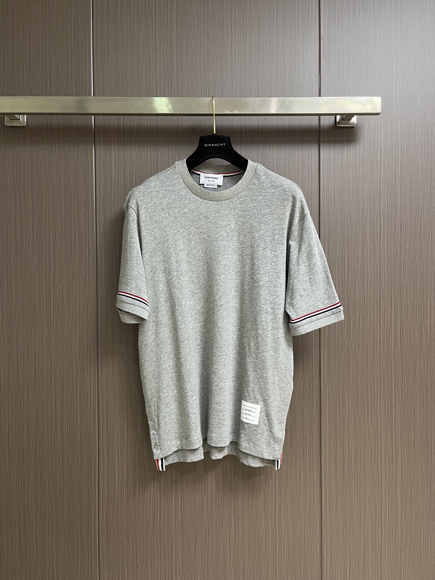 NO:914598,THOM BROWNE TB  Three-color striped round neck short-sleeved T-shirt on the cuffs. This navy T-shirt is made of high-count combed cotton knitted fabric. It feels soft and waxy and has excellent anti-pilling performance. It is comfortable and unrestricted on the upper body. The details of the body are full of ingenuity. The inner lining of the collar is supplemented by a double-layer hot-melt lining for shaping, which will not deform after long-term wear. The edge of the collar is decorated with delicate red, white and blue webbing wrapping technology, which is exquisite and durable; the cuffs are designed with webbing splicing and sharp contrasting lines.  The drop is clear, effectively enhancing the sense of layering of the body; the brand's exclusive sheepskin logo is ingeniously sewn on the inside of the hem, and the side slits on the hem are embellished with the iconic webbing, highlighting the high-end texture in the details. The overall stitching follows high-standard double-needle technology, the stitches are even and tight, and the stitching is firm and not off-line. Every process embodies the elegance and sophistication of high-quality garments. The overall wiring is straight and delicate, the fabric is comfortable and soft, and the colors are consistent and without color difference.  It can be matched with the same style to create a fashionable look, and can be used in various occasions. Customized accessories, complete with three standards, same style for men and women!  Sizes 1 - 2 - 3 - 4 Size 1 Chest 102 Shoulder width 44 Length 68 Sleeve length 24 Size 2 Chest 106 Shoulder width 46 Length 70 Sleeve length 25 Size 3 Chest 112 Shoulder width 48 Length 72 Sleeve length 26 Size 4 Chest 118 Shoulder width 50 Length 74  Sleeve length 27,,T-shirt,tees,t-shirt,sheepskin,19860909THOM BROWNE TB 袖口三色条纹圆领短袖T恤,这款藏青色T恤采用高支数精梳棉针织面料打造,触感软糯且具备优异的抗起球性能,上身舒适无束缚.衣身细节尽显匠心领口内里辅以双层热熔衬定型,久穿不变形,领口边缘饰有细腻的红白蓝织带包边工艺,精致耐看；袖口采用织带拼接设计,撞色线条利落分明,有效提升衣身层次感；下摆内侧匠心缝制品牌专属羊皮标,下摆侧边开衩点缀标志性织带,细节处彰显高级质感.整体车线均遵循高标准双针工艺,线迹均匀紧密,缝合牢固不脱线,每一处工艺都凝聚着高品质成衣的考究与精致.整体走线平直细腻,面料舒适柔软,颜色一致无色差 能与同款搭配营造时尚造型,驾驭各种场合,定制辅料,三标齐全,男女同款！尺码1码-2码-3码-4码 1码 胸围102 肩宽44 衣长68 袖长24 2码 胸围106 肩宽46 衣长70 袖长25 3码 胸围112 肩宽48 衣长72 袖长26 4码 胸围118 肩宽50 衣长74 袖长27,,T-shirt,tees，t-shirt,sheepskin,,Men's clothing