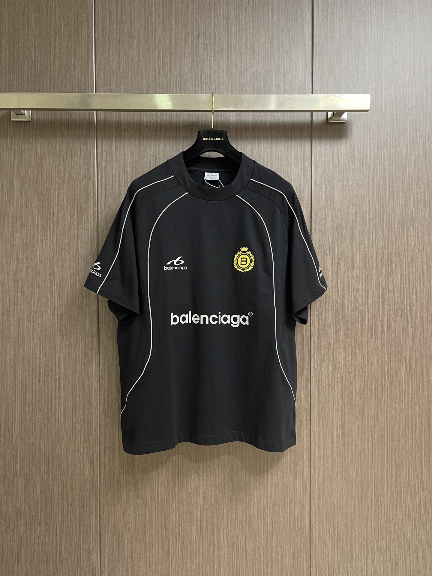 NO:935739,Balenciaga  Manchester United football co-branded short-sleeved T-shirt, this Balenciaga sports-style short-sleeved T-shirt is made of high-count combed cotton fabric, which is soft and breathable to the touch, comfortable and skin-friendly. The overall design is loose and dropped shoulders, with neat and casual lines, and has a relaxed street atmosphere. The body is mainly black, with a white top-line curved edge design, which outlines the classic outline of a sports jersey and restores a retro competitive feel. There is a clear brand letter logo printed on the chest.  The logo and sports style logo are paired with the yellow badge embroidery on the left chest. The embroidery stitches are fine and flat, with bright colors and high-end texture. The neckline adopts reinforced rib technology, which is not easy to deform after long-term wear. The overall workmanship is rigorous, and the wiring is neat and firm. It cleverly combines retro sports aesthetics with the brand's pioneering style. It has both trend recognition and daily practicality, and can easily create a personalized street style. The overall wiring is straight and delicate, the fabric is comfortable and soft, and the colors are consistent and without color difference.  Can be matched with the same style to create a fashionable look, to suit various occasions, customized accessories, complete with three standards!  Size XS-S-M-L19860909Balenciaga 曼联足球联名短袖T恤,这款Balenciaga运动风短袖T恤,甄选高支精梳棉面料打造,触感柔软透气,穿着舒适亲肤.整体采用宽松落肩版型,线条利落随性,自带松弛街头氛围.衣身以黑色为主调,搭配白色明线弧形包边设计,勾勒出运动球衣的经典轮廓,还原复古竞技感.胸前印有清晰的品牌字母标识与运动风logo,搭配左胸黄色徽章刺绣,刺绣针脚细密平整,色彩鲜明,质感高级.领口采用加固罗纹工艺,久穿不易变形,整体做工严谨,走线工整牢固,将复古运动美学与品牌先锋风格巧妙融合,兼具潮流辨识度与日常实穿性,轻松打造个性街头造型.整体走线平直细腻,面料舒适柔软,颜色一致无色差 能与同款搭配营造时尚造型,驾驭各种场合,定制辅料,三标齐全！尺码XS-S-M-L XS码衣长71.5 胸围126 袖长38.8 S码 衣长73胸围130 袖长40 M码 衣长74.5 胸围134 袖长41.2 L码 衣长76胸围138袖长42.4,,balenciaga,T-shirt,tees，t-shirt,,Men's clothing