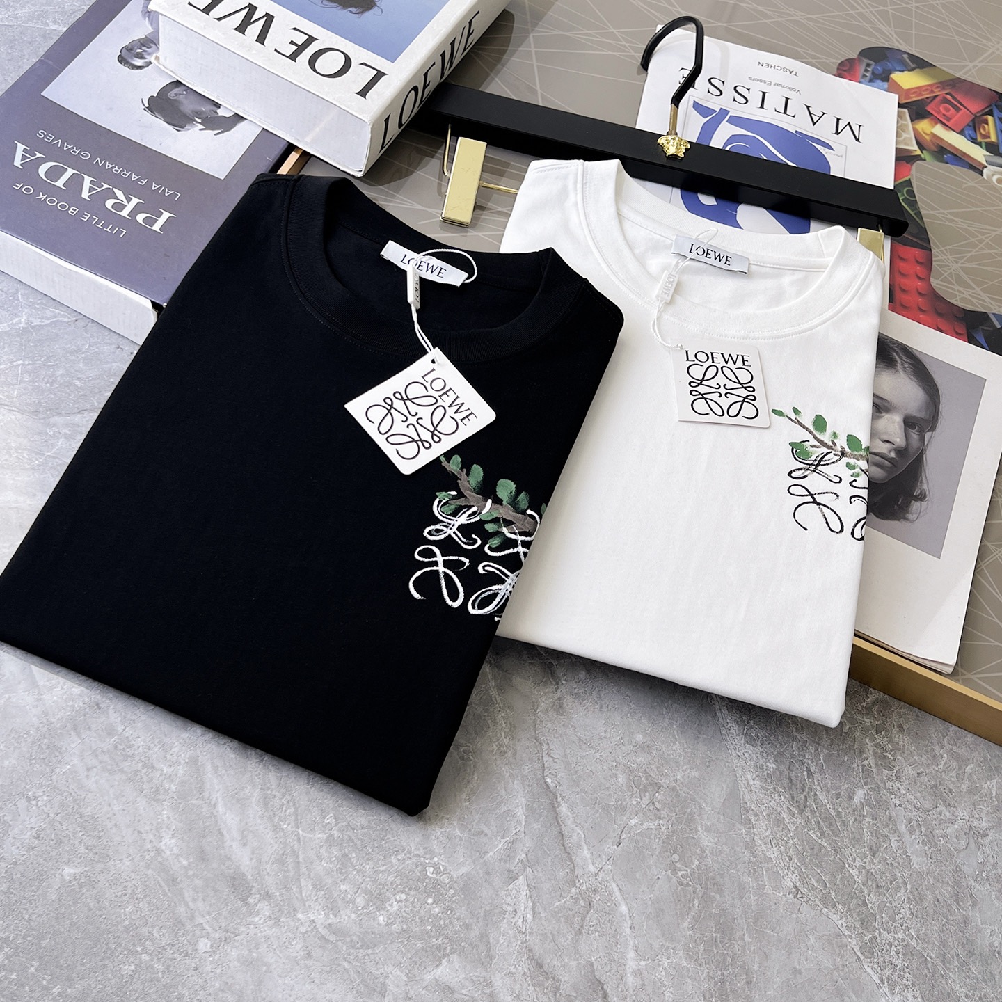 💰100。  Loewe 2025春夏新款首发专柜最新款短袖圆领T恤 高端订制 设计前卫时尚！品牌logo重工艺设计 高端定制面料.手感柔软.穿着舒适.专柜级别精致车线.做工精细.上身效果无敌帅气！型男必备单品！颜色：黑色。白色。码数：S-3XL（下单请报身高体重）