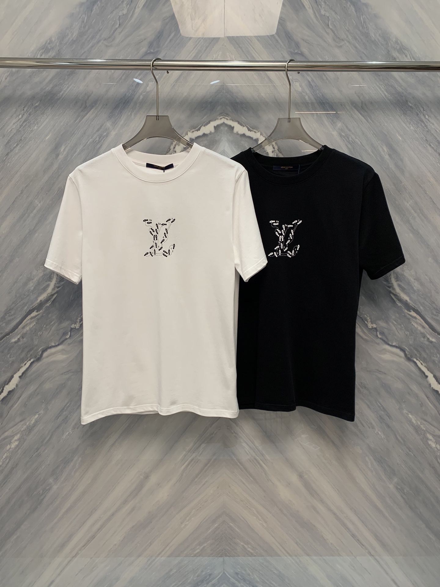 NO:419302,The new spring and summer 1V art print round neck high gram heavy short-sleeved T-shirt. This short-sleeved short-sleeved T-shirt is very exquisite in detail. First of all, it uses high gram heavy cotton material. This fabric is not only soft and comfortable, but also has a certain thickness, which can well maintain the shape of the clothes and not easily deformed. The art print design on the T-shirt is very unique, combining the 1V brand's iconic patterns and modern art elements, showing the classic brand charm and the sense of fashion. The prints are bright and uniform in color, and can still maintain a new effect after multiple washes. In terms of tailoring, this T-shirt focuses on ergonomic design, and the style is fit, which is neither too tight nor too loose, and can well modify the body. The neckline adopts a classic round neck design, which is simple and elegant, suitable for wearing in various occasions. The stitching of the cuffs and hem is exquisite and tight, showing the 1V brand's consistent high-quality craftsmanship. Color: Black White  Size: S-2XL S: Bust 104 Length 70 Shoulder width 44 Sleeve length 23 M: Bust 108 Length 71 Shoulder width 45 Sleeve length 24 L: Bust 112 Length 72 Shoulder width 46 Sleeve length 25 XL: Bust 116 Length 73 Shoulder width 47 Sleeve length 26 2XL: Bust 120 Length 74 Shoulder width 48 Sleeve length 27, T-shirt,tees,t-shirt,alexander wang19860909春夏新品1V艺术印花圆领高克重短袖T恤,这款短袖在细节处理上非常考究.首先,它采用高克重棉质材料,这种面料不仅柔软舒适,还具有一定的厚度,能够很好地保持衣服的形状,不易变形.T恤上的艺术印花设计非常独特,融合了1V品牌标志性的图案与现代艺术元素,既展现了经典的品牌魅力,又不失时尚感.印花的色彩鲜艳且均匀,经过多次水洗后依然能够保持如新的效果. 在剪裁方面,这款T恤注重人体工学设计,版型合身,既不过于紧身也不过于宽松,能够很好地修饰身形.领口采用经典的圆领设计,简洁大方,适合各种场合穿着.袖口和下摆的缝线精致紧密,展现了1V品牌一贯的高品质工艺. 颜色:黑色 白色 尺寸:S-2XL S:胸围104 衣长70 肩宽44 袖长23  M:胸围108 衣长71 肩宽45 袖长24  L:胸围112 衣长72 肩宽46 袖长25  XL:胸围116 衣长73 肩宽47 袖长26  2XL:胸围120 衣长74 肩宽48 袖长27,,T-shirt,tees，t-shirt,alexander wang,Men's clothing