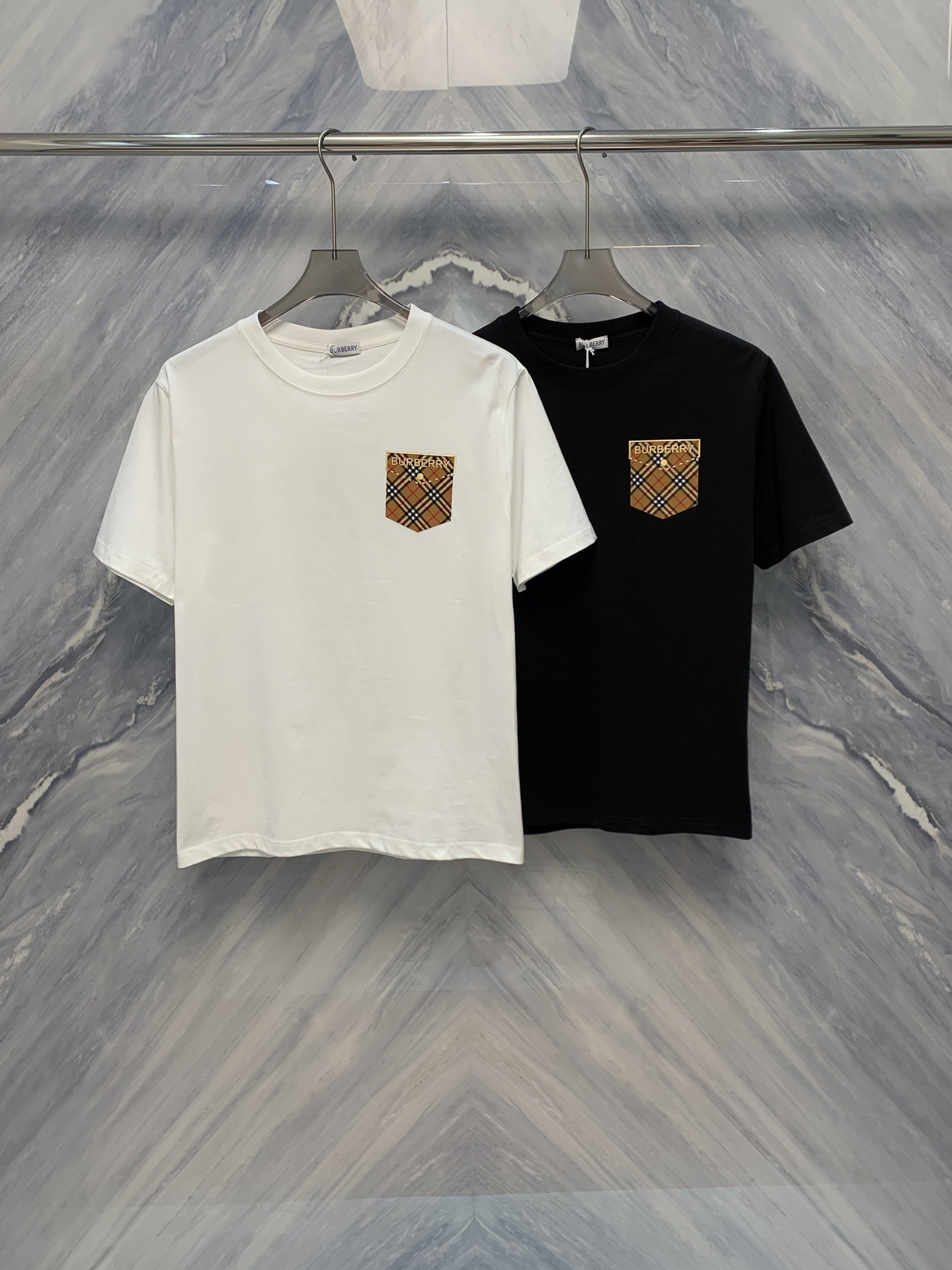 NO:419431,The new 25-spring and summer BBR British plaid cap fake pocket design round neck short-sleeved T-shirt perfectly combines classic and modern elements. Its British plaid pattern originates from traditional Scottish patterns and presents a rich British style. The cap design adds a sense of casualness, while the decorative fake pocket is both practical and fashionable. The round neck design is simple and elegant, suitable for wearing in all occasions. The fabric of the T-shirt is made of high-count cotton material, soft and comfortable, and has good breathability. The plaid pattern adopts advanced printing and dyeing technology, with high color fastness and is not easy to fade. The details of the hat and fake pocket are finely processed and smoothly routed, demonstrating the high-quality craftsmanship level. This T-shirt can be easily controlled. Whether it is matched with jeans, shorts or casual pants. Whether it is for daily travel or vacation, it is your ideal choice. Color: Black White Size: S-2XL  S: Bust 102 Length 69 Shoulder width 45 Sleeve length 21 M: Bust 106 Length 70 Shoulder width 46 Sleeve length 21 L: Bust 110 Length 71 Shoulder width 47 Sleeve length 21 XL: Bust 114 Length 72 Shoulder width 48 Sleeve length 21 XXL: Bust 118 Length 73 Shoulder width 49 Sleeve length 21,,shorts,jeans,T-shirt,tees,t-shirt,hats,alexander wang1986090925春夏新品BBR英伦格纹盖帽假口袋设计圆领短袖T恤,完美融合了经典与现代的元素.其英伦格纹图案,源自传统苏格兰纹样,呈现出浓郁的英伦风情.盖帽设计增添了一份休闲感,而假口袋的装饰则既实用又时尚.圆领设计简约大方,适合各种场合穿着. T恤的面料选用高支数棉质材料,柔软舒适,透气性好.格纹图案采用先进的印染技术,色牢度高,不易褪色.帽子与假口袋的细节处理精细,走线平整,彰显出高品质的工艺水准.这款T恤可随心所欲.无论是搭配牛仔裤、短裤还是休闲裤,都能轻松驾驭.无论是日常出行还是度假休闲,它都是你的理想选择. 颜色:黑色 白色 尺寸:S-2XL S: 胸围102 衣长69 肩宽45 袖长21  M: 胸围106 衣长70 肩宽46 袖长21  L: 胸围110 衣长71 肩宽47 袖长21  XL: 胸围114 衣长72 肩宽48 袖长21  XXL: 胸围118 衣长73 肩宽49 袖长21,,shorts,jeans,T-shirt,tees，t-shirt,hats,alexander wang,Men's clothing