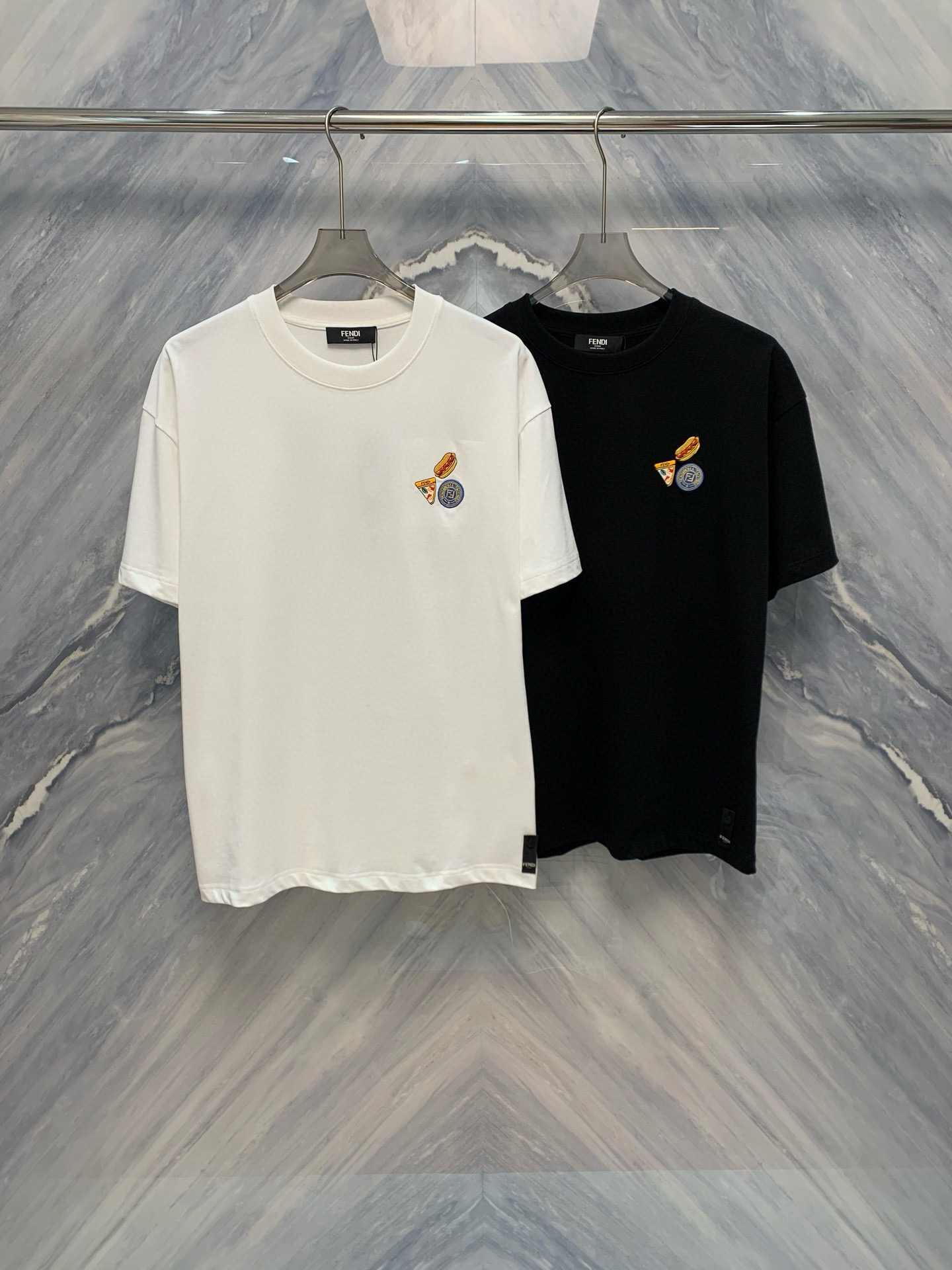 NO:419423,The new FD embroidered logo round neck T-shirt in spring and summer has become the new favorite in the fashion industry with its unique design and excellent quality. It uses pure cotton fabric, which feels soft and breathable, and is extremely comfortable to wear. The biggest highlight of the T-shirt is the embroidered logo on the chest, which is inspired by Fendi's iconic 'hamburger sandwich' pattern. This classic element is vividly presented through exquisite hand-embroidery craftsmanship, which not only retains the brand's high-end texture, but also adds fun and fashion sense. The fine stitching and uniform stitching show the brand's meticulousness in detail, demonstrating the top production process. The loose style design is not only suitable for various body shapes, but also can be easily matched with various bottoms such as jeans and casual pants. Whether it is daily travel or friends' gatherings, you can stand out from the crowd. Color: Black White Size: S-2XL  S: Bust 110, garment length 72, shoulder width 55.5, sleeve length 19.5 M: Bust 114, garment length 73, shoulder width 57, sleeve length 21 L: Bust 118, garment length 74, shoulder width 58.5, sleeve length 22.5 XL: Bust 122, garment length 75, shoulder width 60, sleeve length 24 XXL: Bust 126, garment length 76, shoulder width 61.5, sleeve length 25.5, fendi, jeans,tees, t-shirt, alexander wang1986090925春夏新品FD刺绣Logo圆领T恤以其独特的设计和卓越的品质成为时尚界的新宠.采用纯棉面料,手感柔软且透气性极佳,穿着体验极为舒适. T恤最大的亮点在于胸前的刺绣Logo,其灵感源自于芬迪标志性的“汉堡三明治”图案,通过精湛的手工刺绣工艺将这一经典元素生动地呈现出来,既保留了品牌的高端质感,又增添了趣味性和时尚感 精细的缝线和均匀的针脚展示了品牌对细节的一丝不苟,彰显了顶级制作工艺.宽松的版型设计不仅适合各种体型,还能轻松搭配牛仔裤、休闲裤等多种下装,无论是日常出行还是朋友聚会,都能让你在人群中脱颖而出. 颜色:黑色 白色 尺寸:S-2XL S:胸围110,衣长72,肩宽55.5,袖长19.5  M:胸围114,衣长73,肩宽57,袖长21  L:胸围118,衣长74,肩宽58.5,袖长22.5  XL:胸围122,衣长75,肩宽60,袖长24  XXL:胸围126,衣长76,肩宽61.5,袖长25.5,,fendi,jeans,tees，t-shirt,alexander wang,Men's clothing