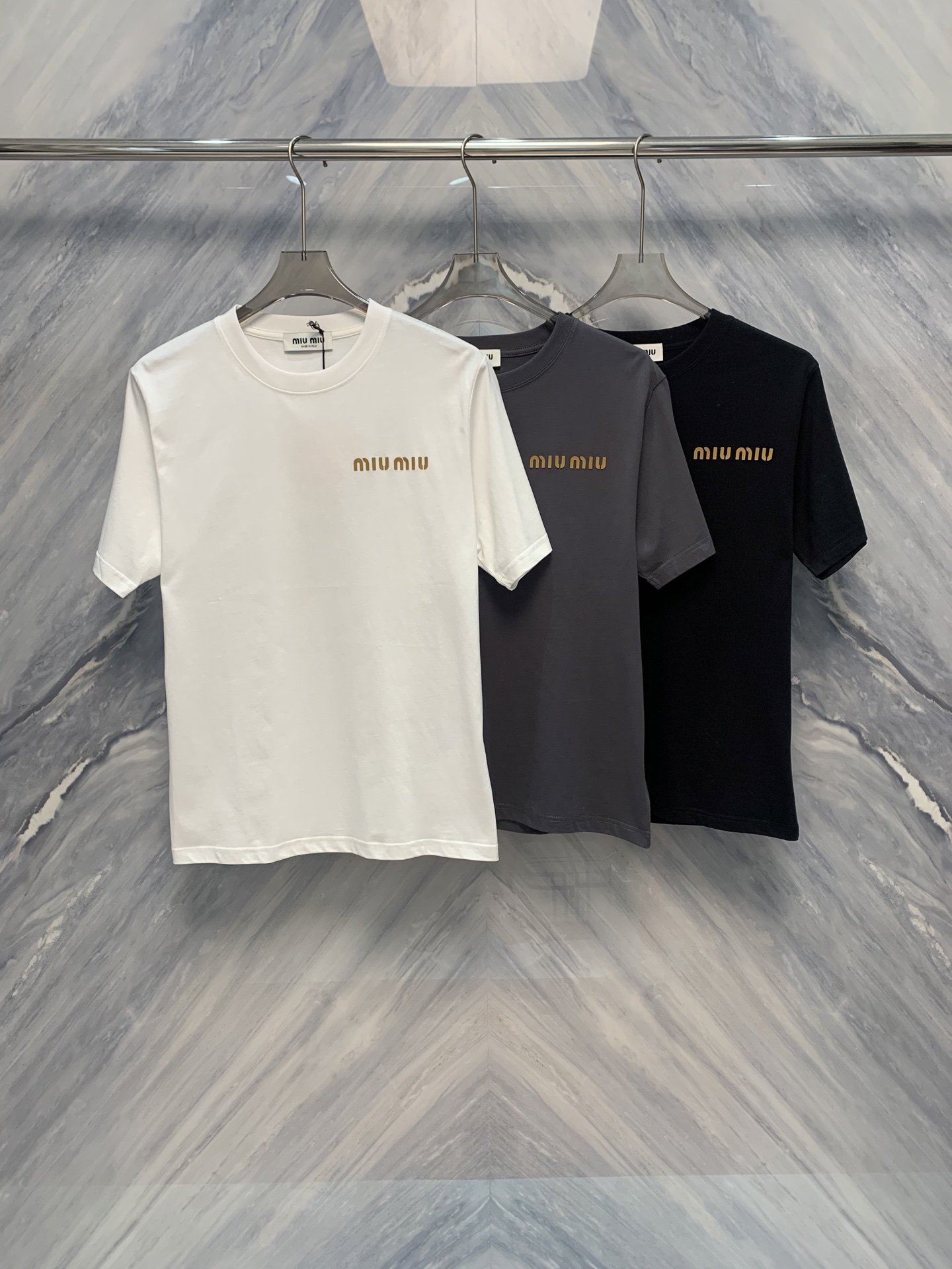 NO:419235,The new spring and summer products are exquisite and comfortable. MIU's round neck embossed cotton short-sleeved T-shirt. In the hot summer, a comfortable and exquisite T-shirt has become a must-have item in the wardrobe. MIU's round neck embossed cotton short-sleeved T-shirt has quickly captured the hearts of fashion enthusiasts with its elegant details and excellent comfort. This T-shirt is made of pure cotton, soft and skin-friendly, and has excellent breathability, and is suitable for summer wear. The overall tailoring of the clothes is simple and smooth, fits the body, showing the wearer's natural beauty.  The classic round neck design is not only durable but also suitable for various occasions. It will not be too ostentatious, and can modify the neck lines just right. The highlight of the T-shirt is its exquisite embossing process, which is full of three-dimensionality and more advanced in light. Whether it is the brand logo on the chest or the details of the cuffs, it reflects the strict quality requirements of MIU. The design of the embossed pattern is inspired by the classic elements of the brand, which is both simple and modern, making the whole T-shirt look particularly exquisite in details. Color: Black White Gray Size: S-2XL S: Bust 102 Length 70 Shoulder width 44 Sleeve length 24 M: Bust 106 Length 71 Shoulder width 45 Sleeve length 25 L: Bust 110 Length 72 Shoulder width 46 Sleeve length 26 XL: Bust 114 Length 73 Shoulder width 47  Sleeve length 27 XXL: Bust 118 Clothes length 74 Shoulder width 48 Sleeve length 28, miumiu, T-shirt,tees, t-shirt,alexander wang19860909春夏新品精致与舒适兼备MIU家圆领压花棉质短袖T恤,在炎炎夏日,一件舒适且精致的T恤成为衣橱中的必备单品.MIU家推出的圆领压花棉质短袖T恤,以其优雅的细节和卓越的舒适度,迅速捕获了时尚爱好者的心.这款T恤采用纯棉材质,柔软亲肤,透气性极佳,适合夏季穿着.衣服的整体剪裁简洁流畅,贴合身形,展现出穿着者的自然美. 经典的圆领设计,不仅耐看还适合各种场合,不会过于张扬,又能恰到好处地修饰颈部线条.T恤的亮点在于其精致的压花工艺,立体感十足,在光线下更显高级.无论是胸前的品牌标识还是袖口的细节处理,都体现了MIU家对品质的严格要求.压花图案的设计灵感源自品牌经典元素,既简约又富有现代感,使整件T恤在细节上显得格外考究. 颜色:黑色 白色 灰色 尺寸:S-2XL S: 胸围102 衣长70 肩宽44 袖长24  M: 胸围106 衣长71 肩宽45 袖长25  L: 胸围110 衣长72 肩宽46 袖长26  XL: 胸围114 衣长73 肩宽47 袖长27  XXL: 胸围118 衣长74 肩宽48 袖长28,,miumiu,T-shirt,tees，t-shirt,alexander wang,Men's clothing