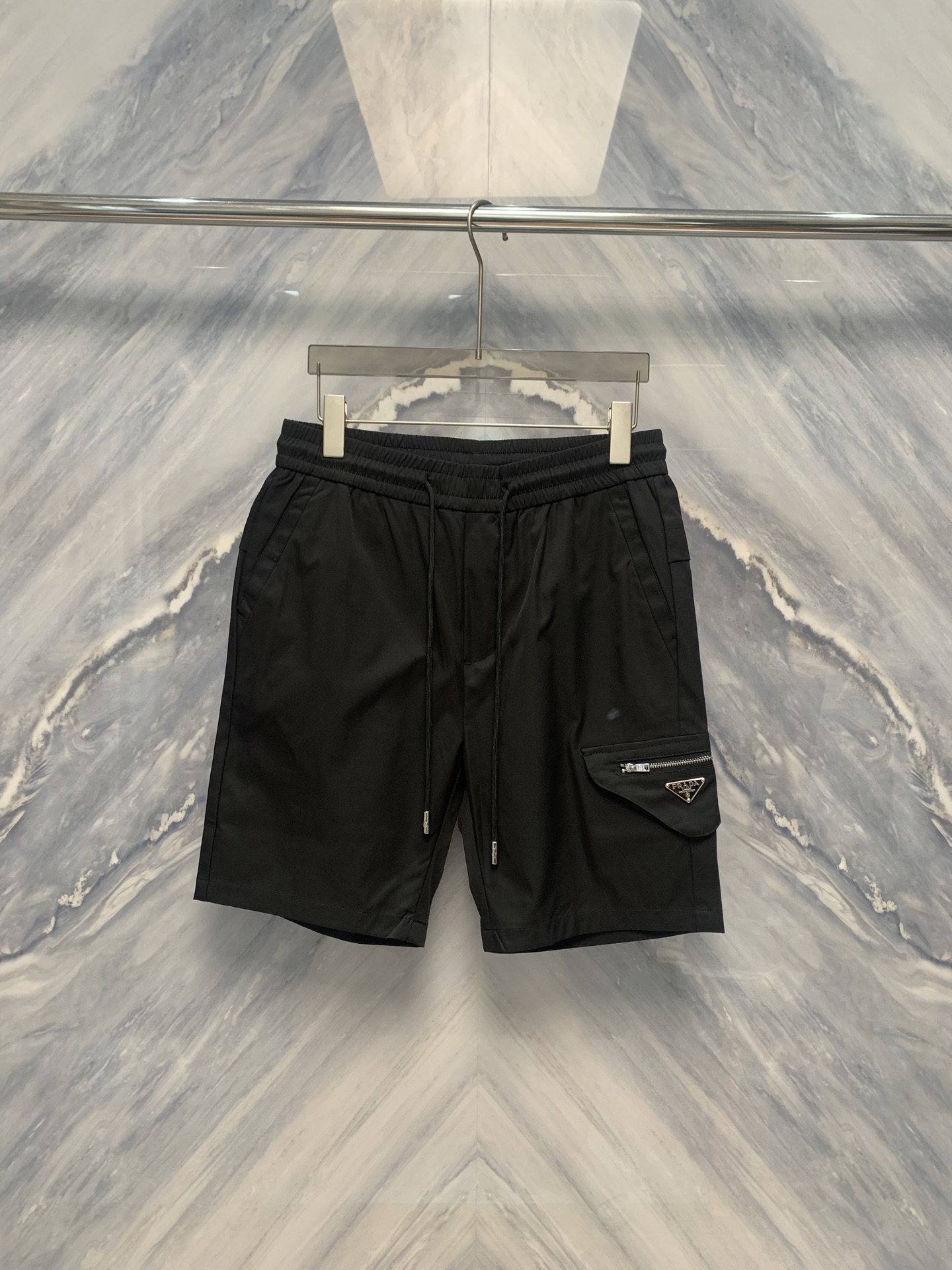 NO:500468,The new Lada inverted triangle logo five-point sports drawstring shorts in spring and summer are a perfect combination of sports and fashion. The design details of this shorts are impressive. From the selection of fabric to the tailoring process, each reflects the ultimate pursuit of quality. The waist of the shorts is designed with drawstring, which is convenient for adjusting elasticity and fits the needs of different body shapes. The inverted triangle logo is located in the middle of the waist, showing the brand identity in a simple and eye-catching way. The logo is printed with a special process, which is not only three-dimensional, but also wear-resistant and not easy to fall off. In terms of fabric, the shorts are made of 51.9 cotton and 48.1 polyester fiber. This combination not only ensures the comfort of wearing, but also has good breathability and durability. Whether it is sports or daily wear, it can be kept refreshing and comfortable. Color: Black Size: M-3XL M: Waist circumference 72 Pants length 48 Hip circumference 102  L: Waist circumference 78 trousers length 49 hip circumference 106 XL: Waist circumference 84 trousers length 50 hip circumference 110 XXL: Waist circumference 90 trousers length 51 hip circumference 114 XXXL: Waist circumference 96 trousers length 52 hip circumference 118,,shorts,alexander wang1986090925春夏新品拉达倒三角Logo五分运动抽绳短裤,是运动与时尚的完美结合.这款短裤的设计细节令人印象深刻,从面料的选择到剪裁工艺,每一处都体现了对品质的极致追求. 短裤的腰部采用抽绳设计,方便调节松紧,贴合不同身型的需求.倒三角Logo位于腰部正中,以简约而醒目的方式展示品牌身份.Logo采用特殊工艺印制,不仅立体感强,且经久耐磨,不易脱落.在面料上,短裤选用了51.9的棉与48.1的聚酯纤维混合材质,这种组合既保证了穿着的舒适度,又具备良好的透气性与耐用性.无论是运动还是日常穿着,都能保持清爽与自在. 颜色:黑色 尺寸:M-3XL M: 腰围72 裤长48 臀围102  L: 腰围78 裤长49 臀围106  XL: 腰围84 裤长50 臀围110  XXL: 腰围90 裤长51 臀围114  XXXL: 腰围96 裤长52 臀围118,,shorts,alexander wang,Men's clothing