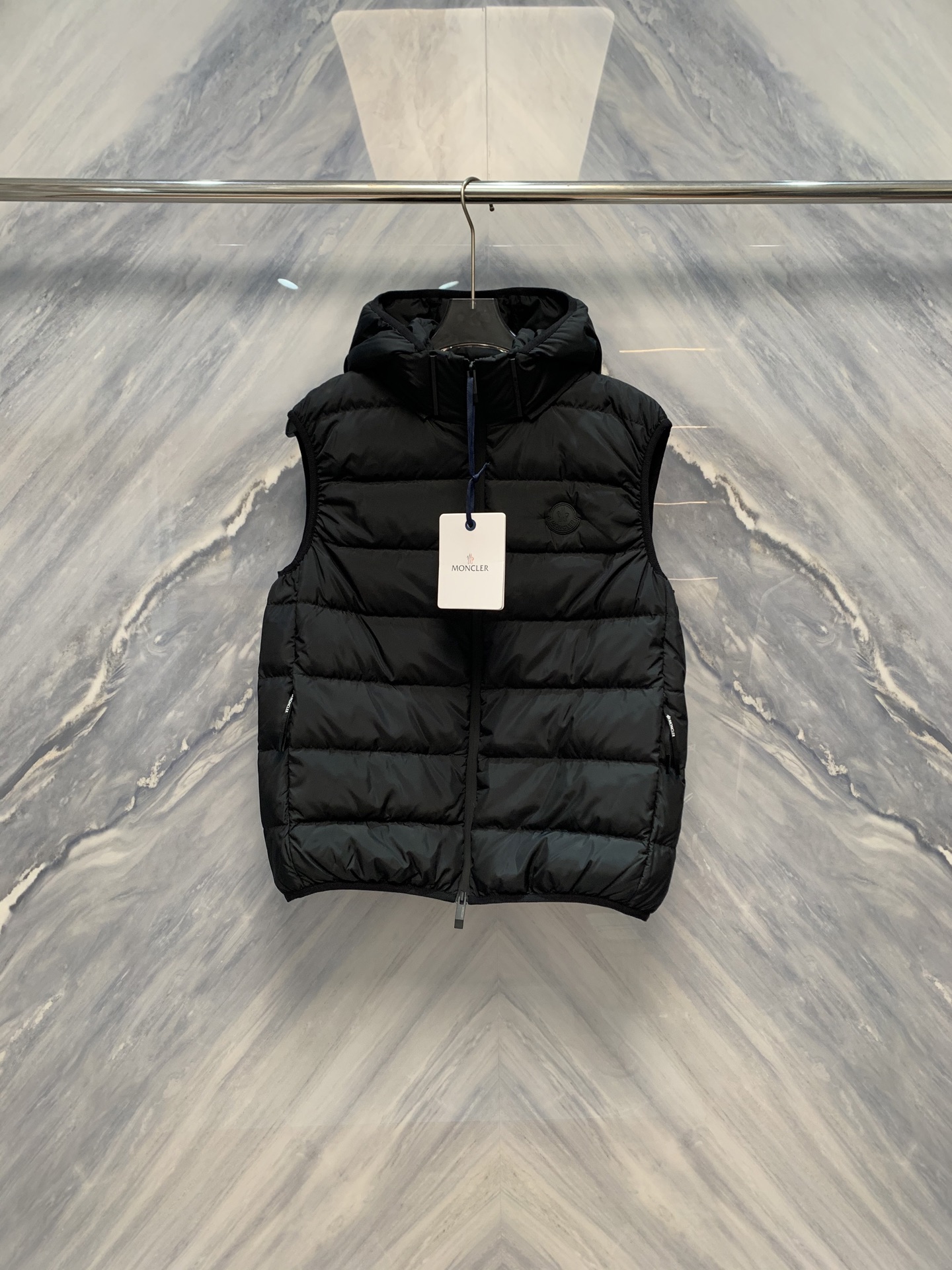 NO:608432,Winter Shield Minimalist Peak M Home Counter Limited Black Label Hooded 90 White Goose Down Vest When the extreme cold comes, the real art of keeping out the cold never relies on complicated stacking, but lies in the precise integration of materials, technology and design. M Home is selling a limited edition over the counter  The classic black label logo hooded down vest redefines the advanced form of winter functional clothing. This vest is the brand's ultimate implementation of the 'less is more' philosophy, and it is also an important wardrobe item that has both aura and practicality in the cold season. The entire piece  The vest is made of high-density windproof and waterproof technical fabric. The surface is slightly shiny like enamel and feels smooth and tough. It can effectively resist the invasion of cold wind and rain and snow penetration, and build an invisible barrier for the wearer. The interior is filled with 90 high-fill white goose down and velvet.  It has huge flowers, long fibers, and is as light as a cloud, but it contains amazing temperature-locking capabilities. Professional testing has shown that its fill power is as high as 750+, and each cubic centimeter can lock a large amount of still air to form a constant-temperature insulation layer, achieving a perfect balance of lightness and warmth.  In terms of design, it continues the M family's iconic minimalist silhouette. The sleeveless cut gives great freedom of layering. It can be easily worn under a coat or a windbreaker, or worn outside a sweatshirt to create a layered urban look. The hood design adopts an adjustable drawstring system. The hood is full and three-dimensional, effectively wrapping the head and neck and resisting crosswinds. In the lower left corner of the chest, a low-key black classic Logo label is quietly embellished. It is not rendered in bright colors, but due to the precise embossing process and material combination  Than, it shows the brand identity that cannot be ignored in silence. There is a hidden zipper pocket inside, which is safe and practical; the hem is equipped with elastic edges to fit the waist and prevent the cold wind from pouring in. The whole garment is neatly routed and has a four-layer structure of anti-drilling velvet gallbladder  , ensuring zero down escape. This limited-edition vest is not only a tool to keep out the cold, but also a modern statement about restraint, functionality and timeless style. In the context of the M family, cold is never a problem, but an opportunity to show off your taste.  Color: Black Size: 1-5 1 Bust 110 Length 66 Shoulder Width 44 2 Bust 114 Length 67 Shoulder Width 45 3 Bust 118 Length 68 Shoulder Width 46 4 Bust 122 Length 69 Shoulder Width 47 5 Bust 126 Length 70 Shoulder Width 48,,hoodie,sweatshirts,down jacket,hats,alexander wang19860909凛冬之盾极简之巅M家柜台限定黑标连帽90白鹅绒羽绒马甲当极寒降临,真正的御寒艺术从不依赖繁复堆叠,而在于材质、科技与设计的精准融合.M家以一件柜台限定发售的经典黑标Logo连帽羽绒马甲,重新定义了冬季机能服饰的高级形态.此款马甲,是品牌对“少即是多”哲学的极致践行,亦是寒冷季节中兼具气场与实穿性的衣橱重器.整件马甲采用高密度防风防水科技面料,表面如釉质般微泛光泽,触感顺滑坚韧,能有效抵御寒风侵袭与雨雪渗透,为穿着者构筑起一道隐形屏障.内里填充90高蓬松度白鹅绒,绒朵硕大,纤维绵长,轻盈如云,却蕴藏惊人锁温能力.经专业检测,其蓬松度高达750+,每一立方厘米皆能锁住大量静止空气,形成恒温隔热层,实现轻盈与保暖的完美平衡. 设计上,延续M家标志性的极简廓形,无袖剪裁赋予极强叠搭自由度,可轻松穿于大衣、风衣之内,亦可外搭卫衣,打造层次分明的都市造型.连帽设计采用可调节抽绳系统,帽型饱满立体,有效包裹头部与颈部,抵御侧风侵袭.胸前左下角,一枚低调的黑色经典Logo标牌悄然点缀,未经亮色渲染,却因精准的压印工艺与材质对比,于沉静中彰显不可忽视的品牌身份.内里设有隐藏式拉链暗袋,安全实用；下摆配以弹性收边,贴合腰身,防止冷风灌入.全衣走线工整细密,四层结构防钻绒胆布,确保羽绒零外逸.这件限定马甲,不仅是御寒工具,更是一件关于克制、功能与永恒风格的现代宣言.在M家的语境中,寒冷从不是困扰,而是一场展现品位的契机. 颜色:黑色 尺寸:1-5 1胸围110 衣长66 肩宽44 2胸围114 衣长67 肩宽45 3胸围118 衣长68 肩宽46 4胸围122 衣长69 肩宽47 5胸围126 衣长70 肩宽48,,hoodie,sweatshirts,down jacket,hats,alexander wang,Men's clothing