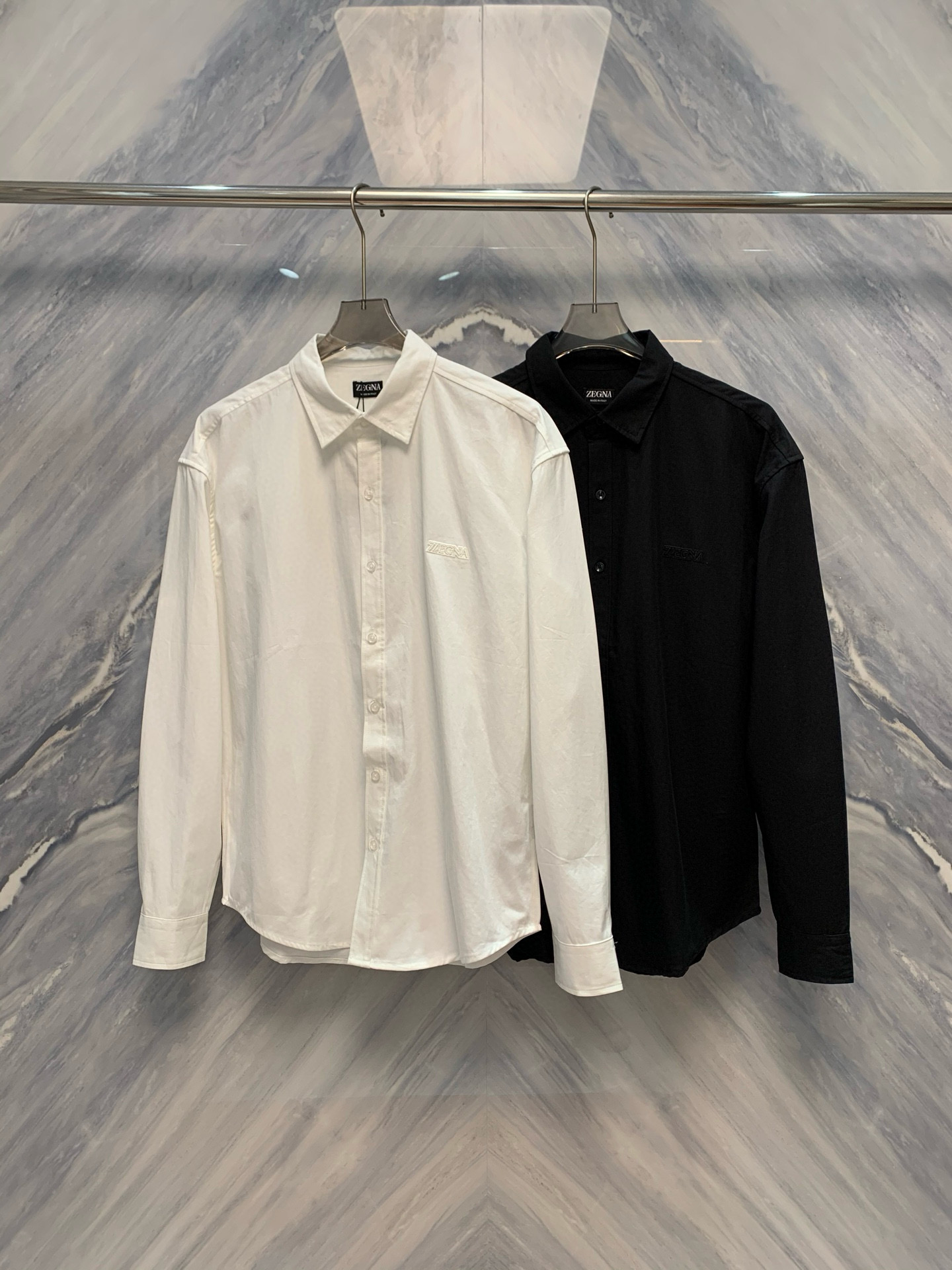 NO:650392,The beginning of elegance and gentility - EZ Early Autumn Men's Cotton Lapel Embroidered Shirt. When the rigor of business meets the calmness of leisure, the EZ brand ingeniously launches a new cotton lapel long-sleeved shirt in early autumn. It uses pure materials and exquisite craftsmanship to write an elegant prelude to the wardrobe of modern men. This shirt is made of high-count long-staple cotton and yarn.  It is fine and even, with a smooth and satin-like surface, soft and skin-friendly touch, and excellent breathability and drape. When the morning light is slightly dewy or the dusk is sinking, every light touch between the skin and the cotton is like a breeze blowing through the wilderness, stretching and natural. The fabric is treated with a pre-shrinking process and will not wrinkle or deform after long-term wear, and can easily cope with multiple scenes of commuting and travel.  The classic lapel design has neat lines and a crisp collar shape. It not only meets the dignified requirements of a formal tie, but can also be unbuttoned to show a casual style with slightly exposed collarbones. The slim cut fits the shoulders and waist curves without cinching the waist.  Tightly bound and free to move, it outlines a restrained and powerful male silhouette when walking, sitting or standing. The finishing touch is hidden on the left chest - the brand's iconic logo is meticulously embroidered with silk threads of the same color, and the stitching is as fine as weaving.  The embroidery is clear and restrained. The embroidery process uses traditional Suzhou embroidery techniques. Each logo takes dozens of minutes to complete by hand. It reveals extraordinary taste in a low-key manner, just like a flower with dark patterns blooming quietly on the skirt. The cuffs are made with real mother-of-pearl buttons.  The buckles are combined, the luster is warm, the opening and closing are smooth, and the details are exquisite. The three-dimensional tailoring and curved hem on the back are both beautiful and practical. Whether you are working at the desk or leaning against the window to enjoy coffee, the shape of the clothes can be kept intact.  Color: White Black Size: S-XL S: Bust 116 Length 72 Shoulder width 53 Sleeve length 63 M: Bust 120 Length 73 Shoulder width 54 Sleeve length 64 L: Bust 124 Length 74 Shoulder width 55 Sleeve length 65 XL: Bust 128 Length 75 Shoulder width 56 Sleeve length 66,,shirts,ties,alexander wang19860909雅序初启绅韵天成——EZ早秋男士棉质翻领刺绣衬衫当商务的严谨邂逅休闲的从容,EZ品牌于早秋之际,匠心推出全新棉质翻领长袖衬衫,以纯粹材质与精微工艺,为现代男性谱写衣橱中的优雅序章.此款衬衫甄选高支长绒棉织造,纱线细密均匀,织物表面光洁如缎,触感柔润亲肤,兼具出色的透气性与垂坠感.在晨光微露或暮色渐沉之际,肌肤与棉的每一次轻触,皆如清风拂过原野,舒展而自然.面料经预缩工艺处理,久穿不皱、不变形,从容应对通勤与差旅的多重场景. 经典翻领设计线条利落,领型挺括有度,既契合正装领带的端庄要求,亦可解开一粒纽扣,演绎微露锁骨的随性风度.修身剪裁贴合肩背与腰身曲线,收腰不紧缚,活动自如,于行走坐立间勾勒出克制而有力的男性轮廓.点睛之笔,藏于左胸位置——品牌标志性logo以同色系丝线精工刺绣,针脚细密如织,纹理清晰而内敛.刺绣工艺采用传统苏绣技法,每一枚徽标皆耗时数十分钟手工完成,低调中透出不凡品位,宛如衣襟上悄然绽放的暗纹之花.袖口以真贝母纽扣缀合,光泽温润,开合顺滑,细节之处尽显考究.后背采用立体剪裁与弧形下摆,兼顾美观与实穿性,无论是伏案工作或倚窗品咖,皆能保持衣型完整如初. 颜色:白色 黑色 尺寸:S-XL S: 胸围116 衣长72 肩宽53 袖长63 M: 胸围120 衣长73 肩宽54 袖长64 L: 胸围124 衣长74 肩宽55 袖长65 XL: 胸围128 衣长75 肩宽56 袖长66,,shirts,ties,alexander wang,Men's clothing