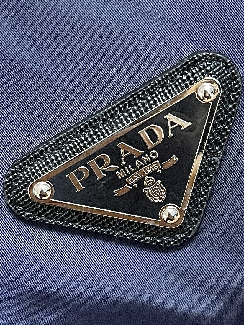 Prada连帽羽绒服面料采用40d尼龙面料尼龙面料轻盈且耐用使得羽绒服既轻便又不易损坏适合各种户外活动和