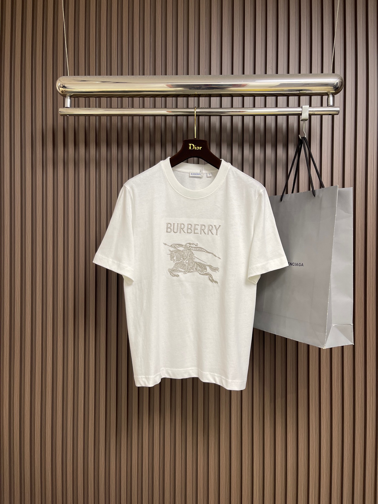 NO:597848,Burberry  Thin-thread war horse embroidery round-neck short-sleeved T-shirt is made of high-quality pure cotton fabric, which is skin-friendly and breathable. The black and off-white tones are classic and versatile. The brand knight logo on the front adopts precision embroidery technology. The silk thread is full in color, the stitching is delicate and three-dimensional, and the pattern is rich in layers, highlighting the brand's high recognition. The round-neck structure is processed by overlocking technology, and the collar fits the neck and is not easy to deform. The body is sewn using industrial-grade flat stitching technology, and the stitches are smooth.  It is uniform, and the stitch length at the hem and cuffs is fine and firm. From the selection of pure cotton fabrics to the control of embroidery details, every process reflects Burberry's pursuit of craft precision and classic style. It not only retains the daily practicality of the T-shirt, but also shows the brand's light luxury recognition through exquisite embroidery. It is a fusion of casual style and exquisite craftsmanship. The overall line routing is straight and delicate, the fabric is comfortable and soft, and the color is consistent without color difference.  It can be matched with the same style to create a fashionable look, and can be used in various occasions. Customized accessories, complete with three standards, same style for men and women!  Size XS-L,,burberry,T-shirt,tees,t-shirt,alexander wang19860909Burberry 细线战马刺绣圆领短袖T恤,选用高品质纯棉面料,触感亲肤透气,黑色与米白色调经典百搭.正面品牌骑士标识采用精密刺绣工艺,丝线色泽饱满、针脚细腻立体,图案层次丰富,彰显品牌高辨识度.圆领结构经锁边工艺处理,领口贴合颈部且不易变形.衣身车缝采用工业级平缝工艺,线迹平整均匀,下摆与袖口处针距细密牢固.从纯棉面料的甄选到刺绣细节的把控,每一道工序都体现Burberry对工艺精度与经典风格的追求,既保留T恤的日常实穿性,又通过精致刺绣展现品牌的轻奢辨识度,是休闲风格与精湛工艺的融合之作.整体走线平直细腻,面料舒适柔软,颜色一致无色差 能与同款搭配营造时尚造型,驾驭各种场合,定制辅料,三标齐全,男女同款！尺码XS-L,,burberry,T-shirt,tees，t-shirt,alexander wang,Men's clothing