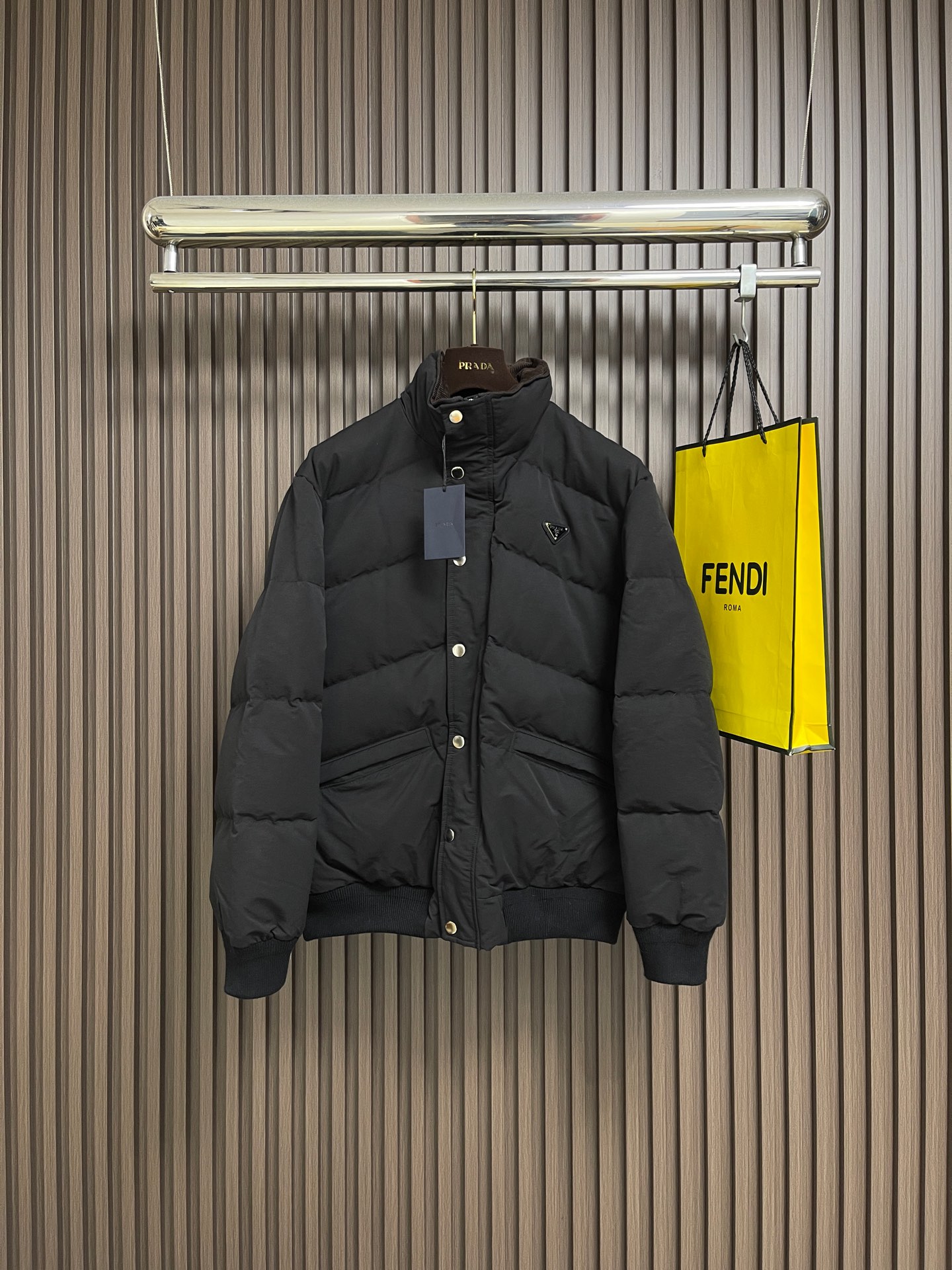 NO:600157,Prada  2025FW new autumn and winter down jacket. The stand-up collar is a luxurious winter hard currency. It is filled with 90% down. The down has high fluffiness and sufficient velvet content. It is lightweight but can lock in heat and get rid of the traditional bloat. It is made of high-count poplin fabric. The matte black tone has a cool and high-end feel. It is windproof and wear-resistant and has a crisp texture. It takes into account environmental protection concepts and practical performance. The classic triangle logo hardware decoration on the chest is used to suppress  The textured leather + metal rivet embellishment is a low-key but eye-catching identity mark; the zippers and snap buttons are engraved with the brand logo, the all-black color scheme is integrated with the fabric, and the texture is hidden in every opening and closing; the stand-up collar + ribbed edge design adapts to different body shapes while locking in warmth. The loose cut can be layered and is a 'universal' for autumn and winter commuting. Sizes 46-52, prada, jackets  & coats,down jacket,alexander wang19860909Prada 2025FW秋冬新品羽绒服外套,立领机能奢感的冬日硬通货,内里填充90绒,绒朵蓬松度高、绒子含量足,轻量却能锁住热量,摆脱传统的臃肿厚重；采用高支府绸面料,哑光黑调自带冷冽高级感,防风耐磨且质感挺括,兼顾环保理念与实用性能.胸前经典三角标五金装饰,以压纹皮革＋金属铆钉点缀,是低调却醒目的身份标识；拉链、按扣均刻印品牌标识字样,全黑配色与面料融为一体,质感藏在每一处开合；立领＋罗纹收边设计,适配不同身形的同时锁住暖意,宽松剪裁可叠穿、,是秋冬通勤的「万能」.尺码46-52,,prada,jackets & coats,down jacket,alexander wang,Men's clothing