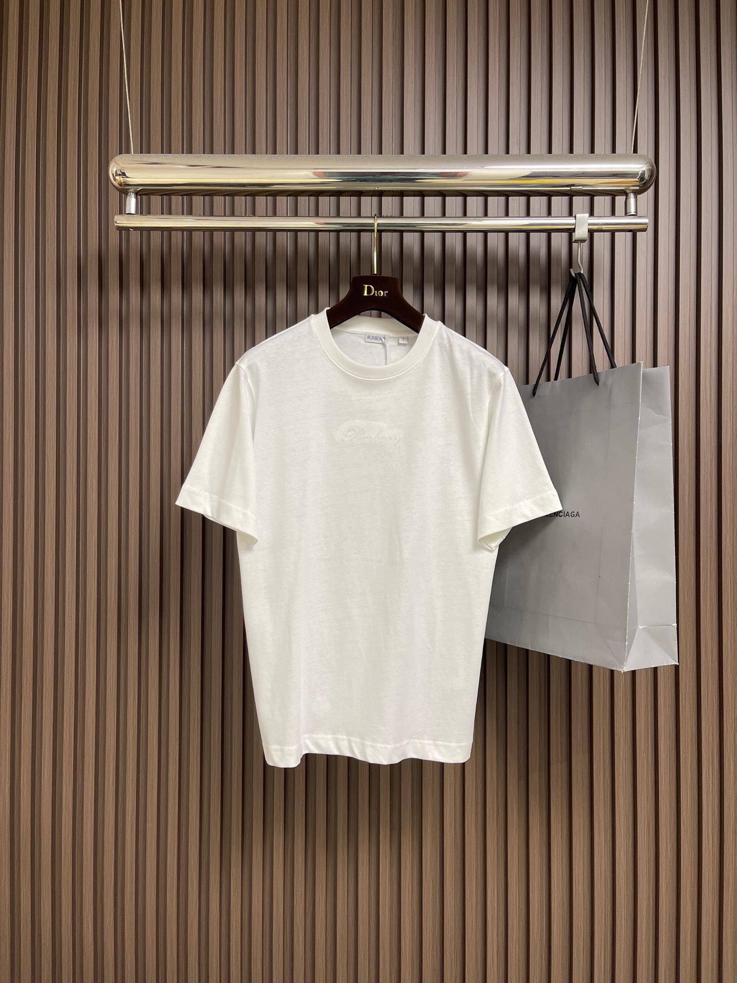 NO:597857,Burberry plaid back letter embroidered round neck short-sleeved T-shirt, made of 15S fine cotton plain weave, white 230g, black 310g; matching  32S double yarn tensioner thread, 300g. Made of pure cotton plain weave fabric, this weave has a tight structure, giving the fabric a crisp texture and excellent durability, while retaining the natural breathability and skin-friendly properties of cotton. The plain weave fabric is not easy to deform and avoid  It avoids an overly baggy casual feel and provides a neater silhouette. The chest and back are embellished with letter logo embroidery, forming a visual rhythm that echoes the front and rear, all presented through chain stitch embroidery technology. These logos are also embroidered with high precision  Craftsmanship ensures clear edges, firmness and durability. The unique embroidery technique, whose stitches are interlocking like a chain, has a stronger three-dimensional sense, softer touch, and a unique texture and luster. Using this process to present the classic plaid pattern is an innovative deconstruction of the brand's traditional elements. It transforms the original flat pattern into a three-dimensional texture with handicraft warmth, which greatly enhances the sophistication and value of the design. The overall wiring is straight and delicate, the fabric is comfortable and soft, and the colors are consistent and without color difference.  It can be matched with the same style to create a fashionable look, and can be used in various occasions. Customized accessories, complete with three standards, same style for men and women!  Size XS-L,,burberry,T-shirt,tees,t-shirt,alexander wang19860909Burberry 格子背字母刺绣圆领短袖T恤,采用15S精棉平纹,白230g、黑310g；搭配 32S双纱拉架螺纹,300g.采用纯棉平织面料,这种织法结构紧密,赋予面料挺括的骨感和优异的耐久性,同时保留了棉天然的透气与亲肤特性.平织面料不易变形,避免了过于松垮的随意感,提供了更为利落的轮廓.前胸及背部均点缀字母徽标刺绣,构成了前后呼应的视觉节奏,均通过链式缝线刺绣工艺呈现.这些徽标同样采用高精度的刺绣工艺,确保边缘清晰、牢固耐用.独特的刺绣技法,其线迹如同链条般环环相扣,立体感更强、触感更柔软,且具有独特的纹理光泽.将经典的格纹图案用此种工艺呈现,是对品牌传统元素的一次创新解构,它将原本平面的图案转化为具有手工艺温度的立体肌理,极大地提升了设计的精致度和价值感.整体走线平直细腻,面料舒适柔软,颜色一致无色差 能与同款搭配营造时尚造型,驾驭各种场合,定制辅料,三标齐全,男女同款！尺码XS-L,,burberry,T-shirt,tees，t-shirt,alexander wang,Men's clothing