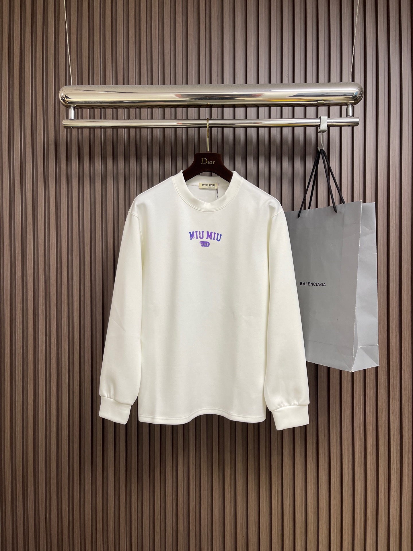 NO:606897,MIUMIU 2025SS round neck long-sleeved T-shirt is made of high-grade 24-count combed cotton yarn. The color uniformity is ensured through the 'first dyeing and then weaving' process. The yarn is double-twisted to improve the pilling resistance, and the cloth surface finish is better than ordinary cotton fabrics. The 190-gram weight of the pattern is precisely controlled and knitted on an 18-needle fine-gauge circular machine, taking into account drape and stiffness. It needs to cooperate with a constant temperature and humidity workshop to avoid yarn tension fluctuations. Compact spinning structure  Drawing on the Swiss Rieter compact spinning technology, the yarn hairiness is reduced by 60, and the fabric density reaches 156 needle inches 2, achieving a baby skin touch while maintaining an elastic recovery rate of more than 8%. Sizes M-3XL, miumiu, tees, t-shirt, alexander wang19860909MIUMIU 2025SS圆领长袖T恤,采用高品级24支精梳棉纱线,通过「先染后织」工艺确保色彩均匀性,纱线经双股加捻提升抗起球性,布面光洁度优于普通棉织物.对版190克重精密调控通过18针细针距圆机编织,兼顾垂坠感与挺括性,需配合恒温恒湿车间避免纱线张力波动.紧密纺结构 借鉴瑞士立达紧密纺技术,纱线毛羽减少60,织物密度达156针英寸2,实现婴儿肌肤触感的同时保持8％以上的弹性回复率.尺码M-3XL,,miumiu,tees，t-shirt,alexander wang,Men's clothing