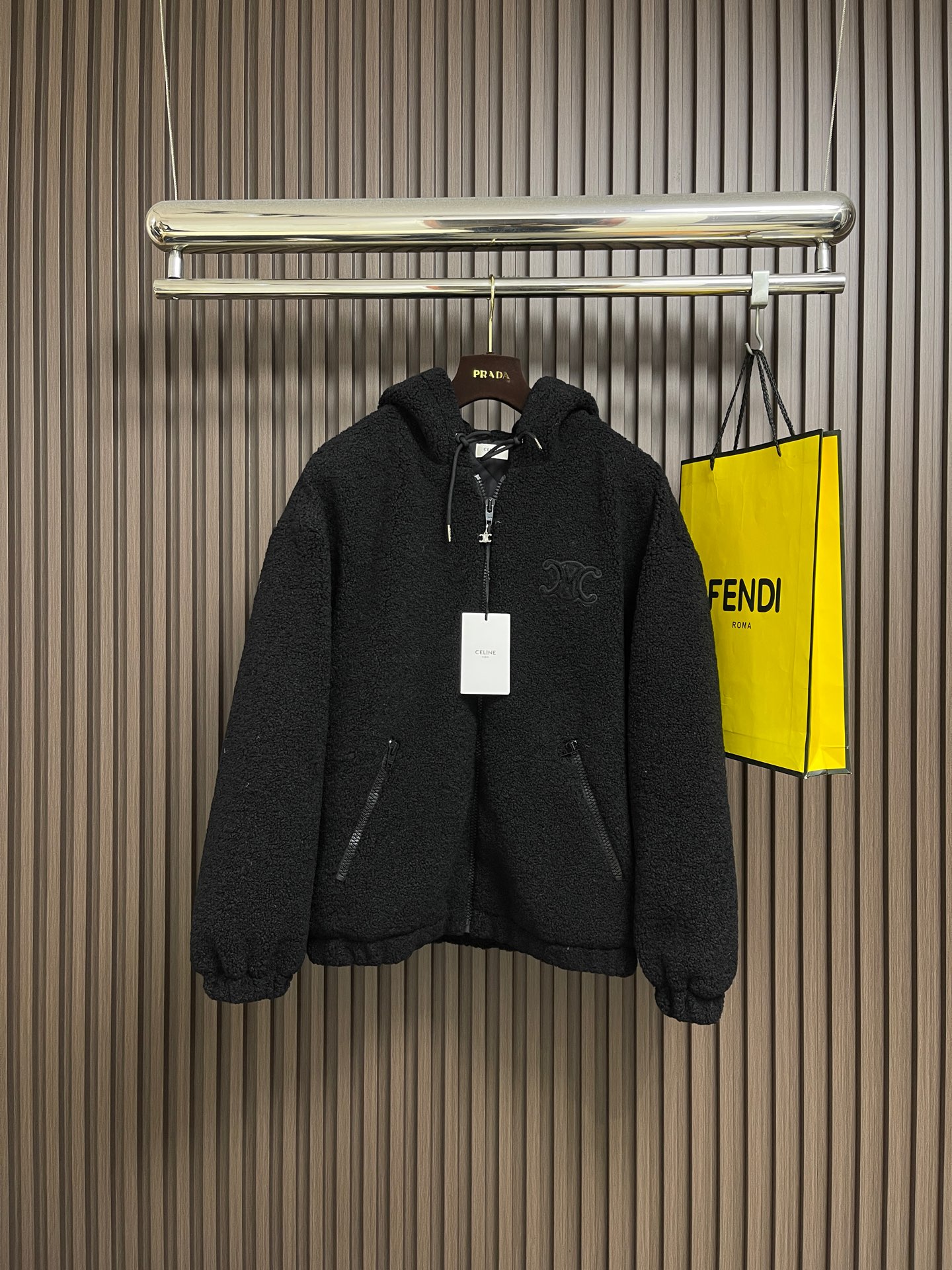 NO:627500,Celine  The suede hooded jacket decorated with the brand logo is made of polyester filament and is knitted through a circular knitting machine. The warp and weft yarns are woven into each other into a double-sided knitted structure. The front and back are flat coils. The fabric is formed after a series of processes such as dyeing, raising, carding, shearing, and polarization. The suede texture is soft.  The fiber characteristics make it almost non-absorbent, and can quickly drain sweat to the outer layer of the fabric and evaporate quickly, maintaining good breathability. The suede surface can lock the air and form a stagnant air layer around the body, effectively preventing heat loss and providing good thermal insulation performance. The inner quilting adopts a quilted cannage pattern, which is precisely adjusted by the seamstress.  The speed and stitch density of the machine make the stitches smooth and even during operation. After completion, regular diagonal quilting lines are formed, which inadvertently improves the overall texture when putting on and taking off. The embroidery patch tightly fixes the fabric and padding material to the frame of the embroidery machine, and the embroidery machine uses sparser stitches along the pattern of the padding layer.  Outline the filling area of the pattern, then run the pattern of the overlay, and use dense stitches to perfectly cover the foam padding layer to form a slightly raised Arc de Triomphe shape. After the final finishing, the edges of the patch are burr-free and the pattern is clear. Sizes S-XL, celine, jackets  & coats,hats,alexander wang19860909Celine 饰品牌标识仔章绒面连帽外套,面料选择涤纶长丝通过针织圆机,将经纱和纬纱相互圈套编织成双面针织结构,正面和背面都是平整的线圈.再通过染色、起毛、梳毛、剪毛、摇粒等一系列流程之后形成的面料.绒面质地柔软,纤维特性使其几乎不吸水,能将汗迅速排到面料外层并快速蒸发,保持良好的透气性.绒面能锁住空气,再身体周围形成一层不流动的空气层,有效防止热量流失,起到良好的保暖性能.内里绗缝采用绗缝藤格纹,缝纫师精确调整机器的速度和针脚密度,作业中线迹平滑、均匀.完成之后形成具有规则的斜向绗缝线条,穿脱时不经意间提升整体质感.绣花贴饰将面料和垫衬材料一同紧绷地固定在绣花机框架上,绣花机沿着垫衬层的版迹运用较稀疏的针迹勾勒出图案的填充区域,紧接着运行覆盖层的版迹,用密集的针迹完美地覆盖在泡沫垫衬层之上,从而形成微凸起的凯旋门形状.最后通过整理之后,贴饰边缘无毛刺,图案清晰.尺码S-XL,,celine,jackets & coats,hats,alexander wang,Men's clothing