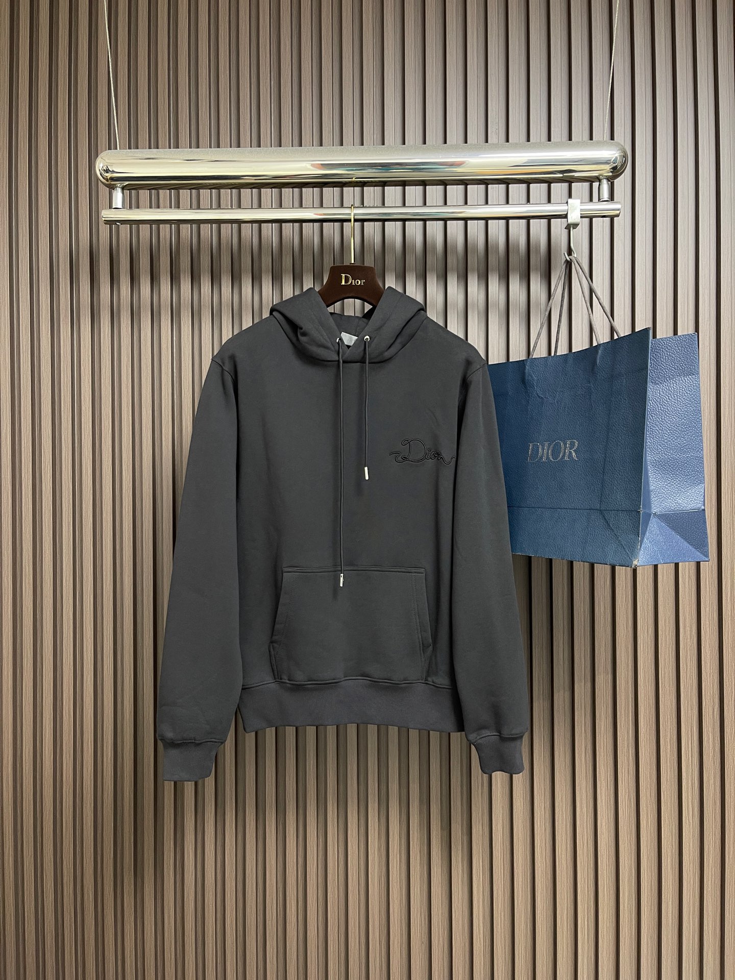 NO:611550,Dior woven satin badge hooded sweatshirt, cotton pile terry fabric, pure cotton texture fabric is made of 26-count double yarn + 10-count base yarn terry fabric, weight 380gm2; matched with 21-count 2x2 Rib, the composition is 95% cotton and 5% spandex; 2.26-count double yarns with a weight of 380gm are used as surface yarns, and the yarns are thinner, ensuring the smooth and smooth appearance of the fabric and good color fastness; while 10-count base yarns are used as terry yarns, and the yarns are thicker, forming loose coils during weaving. After unified raising or brushing treatment in the later stage, a layer of rich, dense and soft velvet is formed on the inside of the fabric. The high weight of wool gives the sweater a heavy drape and crisp texture, making it less prone to wrinkles and stronger styling capabilities. The pure cotton material ensures excellent breathability, moisture absorption and skin-friendly feeling, and the final white color appears pure and rich in texture. The ribbon letter embroidery process brings a multi-dimensional texture. The ribbon itself has a silky luster and smooth touch, which is similar to the matte plush feel of the suede surface of the sweater. A sharp and high-end contrast. The embroidery decoration in the form of ribbons is fixed on the fabric through special processing. The texture brought by this process is usually different from the woven texture and slight luster of the main knitted fabric. It forms a delicate and accessible visual and tactile focus on the matte dark gray base, which enhances the craftsmanship and uniqueness of the single product. Hooded drawstring loose fit design . The classic drawstring hoodie is embellished with an engraved bell, and the hood is equipped with engraved hardware accessories; the cuff threads are the same color as the hood. Restore the original design H silhouette, with kangaroo pockets and open-stitch pockets; the sleeve length is longer than normal for more effect, highlighting the casual sex of the upper body. Sizes XS-L, dior, hoodie, sweatshirts, hats, alexander wang19860909Dior 织缎徽章连帽卫衣,棉质起绒毛圈面料,纯棉质感面料采用26支双纱＋10支底纱的毛圈绒面料,克重380gm2；搭配采用21支 2x2 罗纹,成分為95％棉与5％氨纶；克重380gm2.26支双纱作为表面纱线,纱线更细,确保了面料外观的细腻平整与良好的色牢度；而10支底纱作为毛圈纱,纱线更粗,在织造时形成松散的线圈,经后期统一的起绒或刷绒处理后,在面料内侧形成一层丰厚、浓密且柔软的绒毛.的高克重赋予了卫衣重磅的垂坠感和挺括的骨感,使其不易褶皱,造型能力更强.纯棉的材质保证了极佳的透气性、吸湿性和亲肤感,最终的白色呈现纯净且富有质感.缎带字母刺绣工艺,工艺带来的多维度质感.缎带本身具有丝质的光泽与顺滑触感,与卫衣起绒面的哑光毛绒感形成鲜明而高级的对比.缎带形式的刺绣装饰,通过工艺特殊处理,使织带固定在面料上.这种工艺带来的质感通常是不同于主体针织面料的梭织质感与轻微光泽,在哑光的深灰色底上形成一个精致而触手可及的视觉与触觉焦点,提升了单品的工艺设计和独特性.连帽抽绳宽松版型设计.经典抽绳帽衫刻字吊钟点缀,帽口设有刻字五金配件；袖口螺纹与帽位同色同缸.还原版型设计H廓形,配合袋鼠袋明线口袋；袖长比常规偏长一些更有效果,突出上身的随性感.尺码XS-L,,dior,hoodie,sweatshirts,hats,alexander wang,Men's clothing