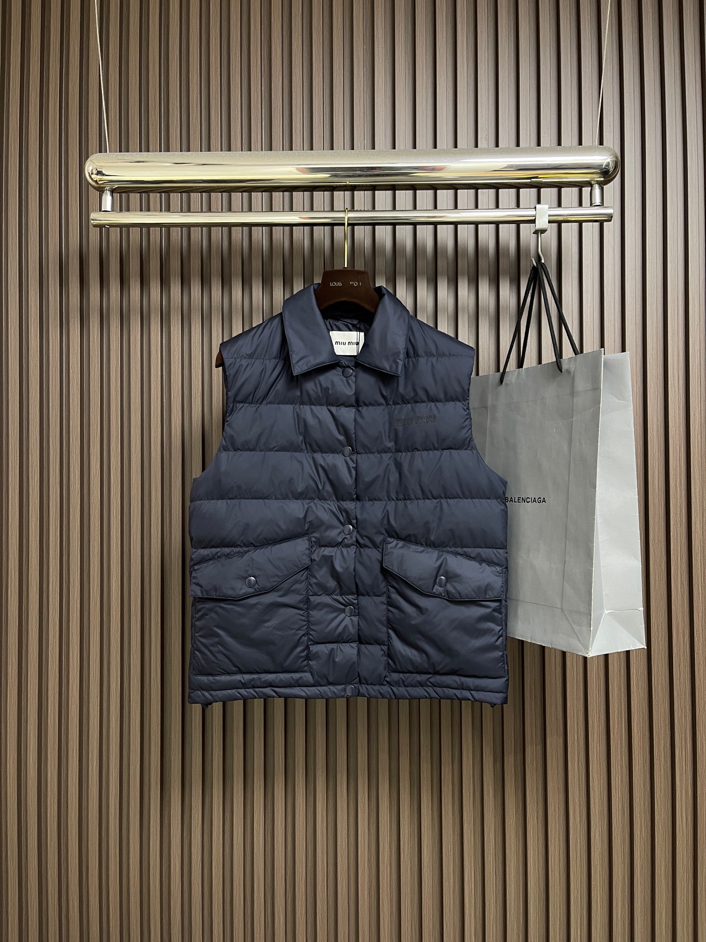 NO:627590,MIUMIU  Quilted down vest sleeveless vest, this down reinterprets outdoor style through functional technical fabrics and styling research. It can be worn alone or used as an inner layer in bold combinations. It uses ultra-light recycled polyester fiber as the base material and is treated with Teflon ecological coating to achieve level 5 water-repellent performance. It is filled with national standard certified white goose down and forms a unique structure through a three-dimensional vertical lining structure.  The vertical temperature-controlled cabin can still maintain a stable core body temperature in low-temperature environments. The surface of the fabric is treated with microporous moisture permeability, and the moisture transmittance can reach 5Lm2·24h. The inner lining is made of anti-static warp and weft knitted fabric to eliminate static electricity problems caused by down friction. The logo uses retro lamination transfer technology, and the hot pressing temperature is adjusted between 115-125°C.  , making the thin polyurethane show a micro-cracked texture that has been used for many years. The edges of the pattern are precisely laser etched to ensure that it remains intact in extreme environments. An innovative grafting process is used to combine the collar shape with outdoor functions. The collar has a built-in flexible support piece to ensure that the collar remains elegant and upright in any stacked state. The front placket is equipped with 5 sets of opening and closing buttons, which can be opened and closed multiple times to maintain 9  4% bite force enables a second-level putting on and taking off experience. The flap pocket uses three-dimensional molding technology, and the opening and closing buttons are integrated on the three-dimensional bag cover through eight processes. The hem has a built-in elastic drawstring structure, using a core-spun rope and a self-locking adjuster, and the windproof sealing adjustment can be completed with one hand. Sizes 36-38-40-42,,miumiu,down  jacket,alexander wang19860909MIUMIU 绗条羽绒马甲无袖背心,这款羽绒通过功能性技术面料和造型研究重新诠释户外风格,可单独穿着或作为内层搭配大胆组合.选用超轻再生聚酯纤维作为基材,经特氟龙生态涂层处理实现5级防泼水性能.内充国标认证白鹅绒,通过立体立衬结构形成独立温控舱室,在低温环境下仍能保持核心体温稳定.面料表面进行微孔透湿处理,湿气透过率可达5Lm2·24h.内衬使用抗静电经纬编面料,消除羽绒摩擦产生的静电困扰.徽标采用复古压胶转印工艺,通过调控热压温度在115-125℃区间,使聚氨酯薄呈现经年使用的微裂纹理.图案边缘进行精准激光蚀刻,确保在极端环境下仍保持完整形态.创新采用领型与户外功能的嫁接工艺,领座内置柔性支撑片,确保领口在任何叠穿状态下保持优雅立挺.前襟配置5组开合纽扣,多次开合保持94％的咬合力度,实现秒级穿脱体验.翻盖口袋运用三维成型技术,通过八道工序开合纽扣整合在立体袋盖上.下摆内置弹力抽绳结构,采用包芯绳与自锁调节器,单手即可完成防风密封调节.尺码36-38-40-42,,miumiu,down jacket,alexander wang,Men's clothing