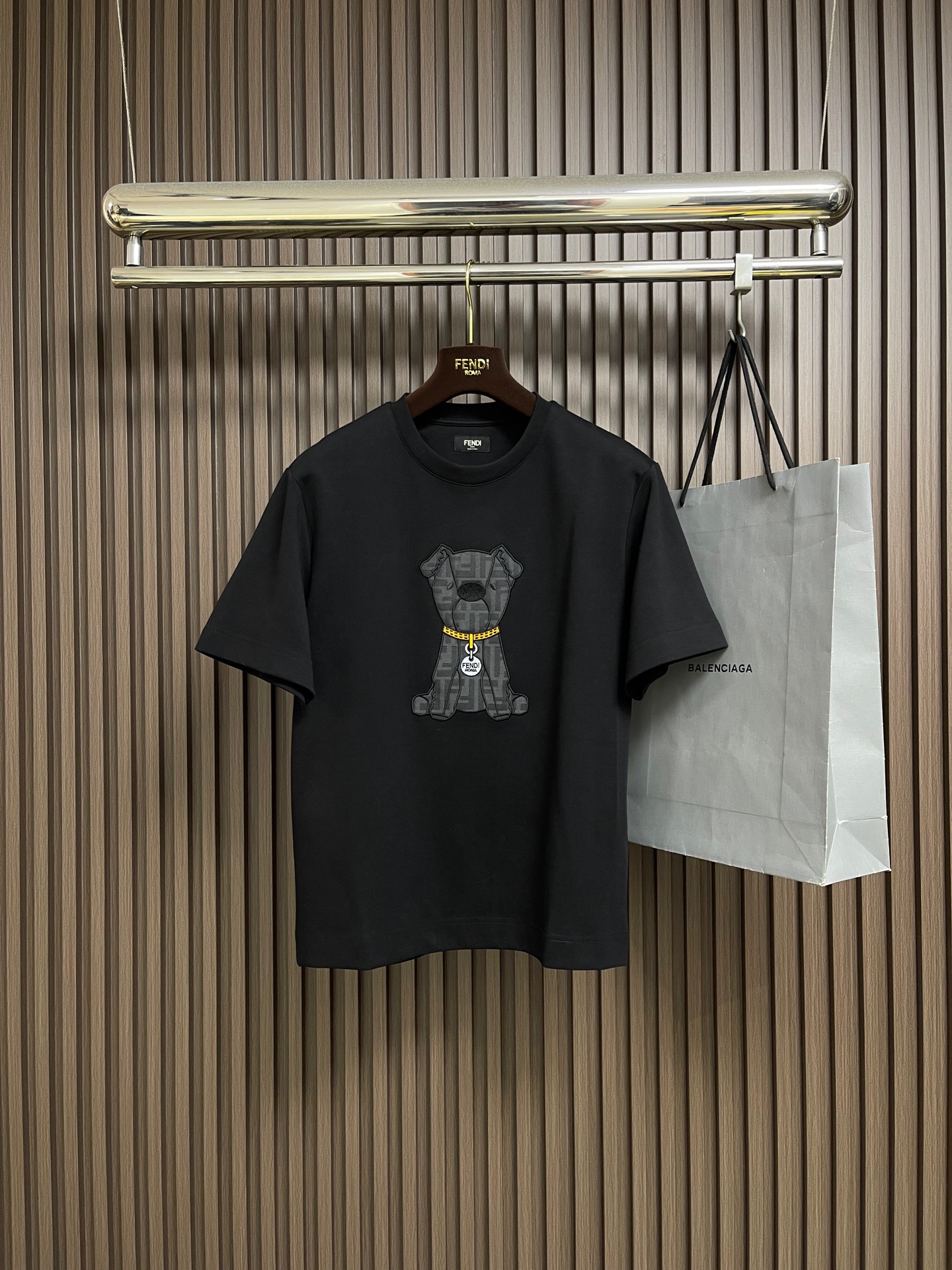 NO:627558,Fendi Bear embroidery round neck short-sleeved T-shirt is made of 32-count single-yarn double-sided fabric with a weight of 280gm. The 2.32-count yarn ensures the delicate feel and tightness of the fabric. The weight of 280g is a heavy fabric, which gives the T-shirt excellent stiffness and drape, and is not easy to wrinkle and deform. The main function of adding 25% polyester is to significantly enhance the surface. The strength, wrinkle resistance and shape retention ability of the material make it more durable than pure cotton fabrics and have a lower shrinkage rate. 75% cotton continues to provide good skin-friendly feel, breathability and moisture absorption. The FF pattern itself is interwoven with yarns of different colors through a jacquard loom, which makes the pattern and the patch base seamlessly integrated. Permanent three-dimensional effect and excellent color fastness. Patch embroidery then fixes this pre-woven jacquard patch to the chest of the T-shirt through the appliqué process. The function of this step is to quickly create a large-area decorative area with a completely different texture from the main fabric, forming a strong visual focus and layering. The patch embroidery covers the edges of the patch The edge is covered with stitch embroidery to fix all edges of the patch to prevent it from rolling up or unraveling in the future, which greatly enhances the durability; through the exquisite and neat embroidery thread outline, the shape of the FF logo is further outlined and strengthened, improving the overall craftsmanship. The overall line routing is straight and delicate, the fabric is comfortable and soft, and the colors are consistent and without color difference. It can be matched with the same style to create a fashionable look, and can be used in various occasions. Customized accessories, complete with three standards, same style for men and women! Size XS-L,,fendi,T-shirt,tees,t-shirt,alexander wang19860909Fendi 小熊刺绣圆领短袖T恤,采用32支单纱双面布,克重280gm2.32支纱线保证了面料的细腻手感和紧实度,280g的克重属于重磅面料,赋予T恤优异的挺括感和垂坠性,不易褶皱变形.25％涤纶的加入,主要作用是显著增强面料的强度、抗皱性和形状保持能力,使其比纯棉面料更耐穿洗,且缩水率更低.而75％的棉则继续提供了良好的亲肤感、透气性和吸湿性.FF图案本身是通过提花织机,使用不同颜色的纱线交织而成,这使得图案与贴片基底浑然一体,具有永久的立体感和卓越的色牢度.贴布绣然后将这块预先织造好的提花贴片,通过贴布绣工艺固定于T恤胸前.这一步的作用是快速建立一个大面积、且质感与主体面料完全不同的装饰区块,形成强烈的视觉焦点和层次感.挨针绣覆盖在贴片的边缘,使用挨针绣进行覆盖锁边,固定贴布的所有边缘,防止其日后卷起或开脱,极大地增强了耐用性；通过精致整齐的绣线轮廓,进一步勾勒和强化FF标识的形态,提升整体的工艺精致度.整体走线平直细腻,面料舒适柔软,颜色一致无色差 能与同款搭配营造时尚造型,驾驭各种场合,定制辅料,三标齐全,男女同款！尺码XS-L,,fendi,T-shirt,tees，t-shirt,alexander wang,Men's clothing