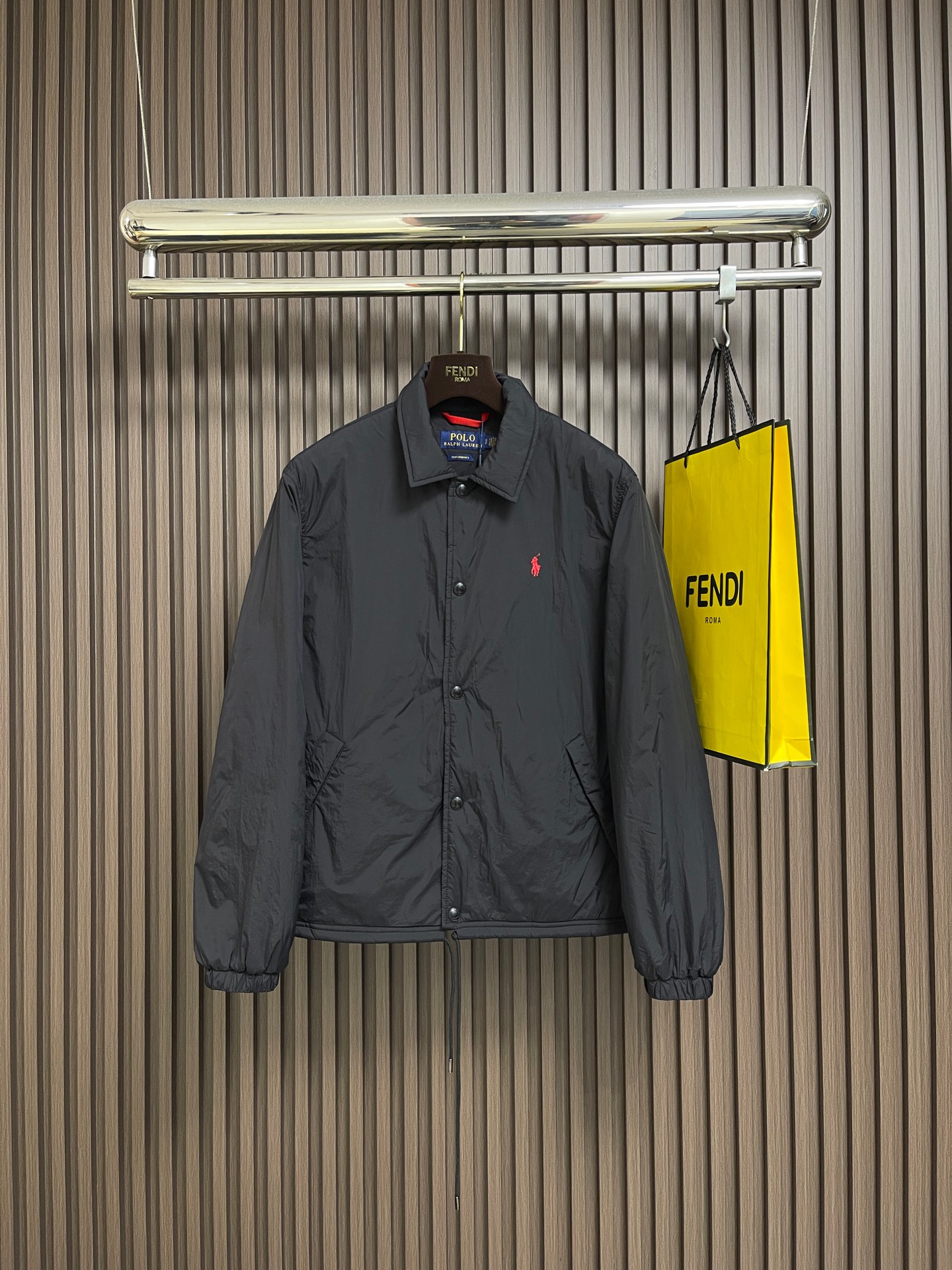 NO:627544,Ralph Lauren red label light cotton coach jacket, made of high-density nylon taffeta with a density of about 210T-300T, with a smooth and slightly matte surface, excellent windproof and waterproof performance (with R water-repellent treatment), strong wrinkle resistance and easy care, in line with the positioning of American casual 'durable and practical'. Classic dark black, using a vat dyeing process (dye penetrates into the fiber), with color fastness up to ISO  Level 4 or above, avoid fading or color transfer after washing. Lightweight cotton-polyester blend lining (65 Polyester + 35  Cotton) reduces the friction between the fabric and the inner clothing, improving the smoothness of wearing. The blended material has both breathability and durability, and avoids the stuffy feeling of pure nylon lining. The classic coach jacket (Jaet) has a loose fit, slightly dropped shoulder line (the shoulder width is 1-2cm wider than the standard version), and the length reaches the hips. The sleeves are slightly tapered straight sleeves, taking into account freedom of movement and casual style. The satin stitch on the left chest horse mark plane  Embroidery (satin embroidery), the embroidery thread is made of polyester high color fastness embroidery thread (the color number is consistent with the brand's standard red color card), the stitch density is 12-15 stitches cm, the outline of the horse mark is clear, and the details of the rider and horse are burr-free. The embroidery positioning is accurately positioned through the template (12cm from the bottom of the collar, 8cm from the placket) to ensure left and right symmetry  And centered. The seams of the top-stitched body are made of double-needle flat seams (needle spacing 3cm and 10 needles). The stitches are smooth and straight. The stitching color is dark black (the same color as the fabric). The stitch width is 0.5cm, which enhances the firmness while forming simple decorative lines. The front placket and the body are spliced with double-layer folding + flat seam splicing.  The thickness is about 0.3cm to ensure that the buttons are not easily deformed when fixed; the edges of the placket are cut with a hot knife to avoid burrs. The armholes where the sleeves and body are joined are round-headed keyhole machine seams + flat seams. After splicing, the armholes have a natural curvature and no sense of tightness when moving; the sleeve mountain height is about 8-10cm, which is in line with the loose characteristics of casual jackets.  The main button is a black urea resin button with a matte surface. The buttonhole is a hand-made keyhole (6 strands of cotton thread, keyhole density 8 stitches mm), and the edge of the eyelet is smooth and has no burrs. The first button on the collar is a hidden button (diameter 12mm), which prevents the collar from opening and improves the neatness of the dress. Size S-XL, loro  piana,jackets & coats,jackets & coats,alexander wang19860909Ralph Lauren 拉夫劳伦 红标轻薄棉服教练夹克外套,高密度尼龙塔夫绸密度约210T-300T,表面光滑微哑光,防风防水性能优异（经R防泼水处理）,抗皱性强且易打理,符合美式休闲'耐穿实用'的定位.经典藏黑色,采用缸染工艺（染料渗透纤维内部）,色牢度达ISO 4级以上,避免洗涤后褪色或串色.轻薄棉涤混纺里布（65 Polyester + 35 Cotton）减少面料与内搭衣物的摩擦,提升穿着顺滑度,混纺材质兼顾透气性与耐用性,避免纯尼龙内衬的闷热感.经典教练夹克（Jaet）宽松版型,肩线微落（肩宽比标准版型宽1-2cm),衣长至臀部,袖型为微锥度直筒袖,兼顾活动自由度与休闲风格.左胸马标平面 satin stitch 刺绣（缎面绣）,绣线采用涤纶高色牢度绣线（色号与品牌标准红色色卡一致）,线迹密度12-15针cm,马标轮廓清晰,骑手、马匹细节无毛刺.刺绣定位通过模板精准定位（距离领口下12cm,距门襟8cm),确保左右对称且居中.明线工艺衣身接缝处采用双针平缝（针距3cm10针）,线迹平整笔直,缝线颜色为藏黑色（与面料同色）,线迹宽度0.5cm,增强牢固度的同时形成简洁的装饰性线条.前襟与衣身拼接门襟处采用双层对折＋平缝拼接,厚度约0.3cm,确保纽扣固定时不易变形；门襟边缘用热切刀切割,避免毛边.袖片与衣身拼接袖窿处采用圆头锁眼机锁边＋平缝拼接,拼接后袖窿弧度自然,活动时无紧绷感；袖山高度约8-10cm,符合休闲夹克的宽松特性.主纽扣黑色尿素树脂扣,表面哑光处理,纽扣孔为手工锁眼（6股棉线,锁眼密度8针mm),孔眼边缘光滑无毛边.领部纽扣领口第一颗纽扣为隐藏式暗扣（直径12mm),防止领口敞开,提升穿着整洁度.尺码S-XL,,loro piana,jackets & coats,jackets & coats,alexander wang,Men's clothing