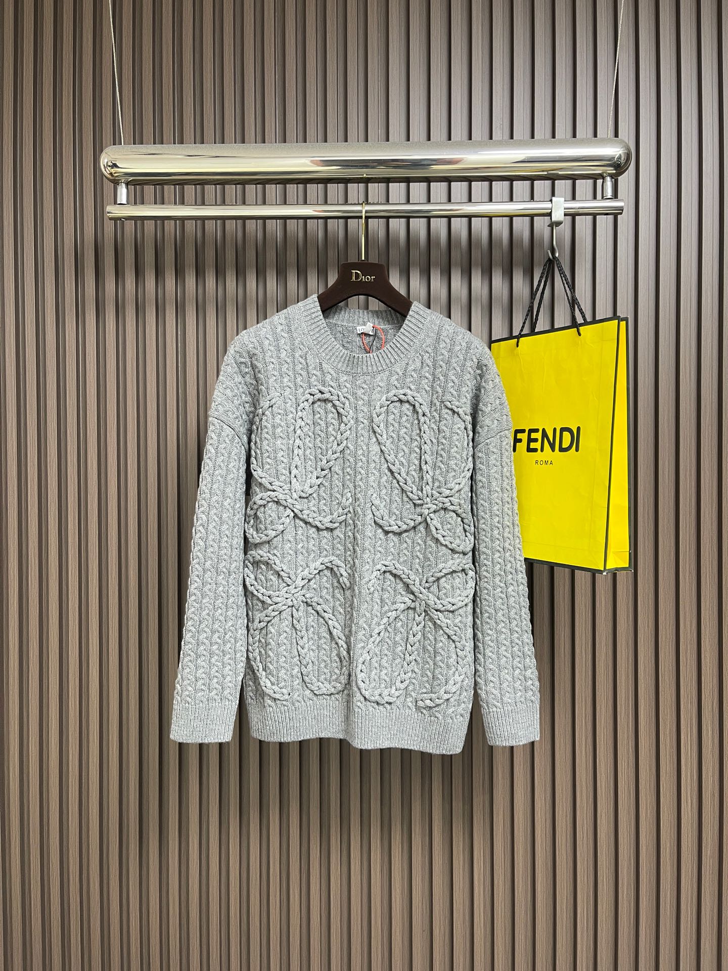 NO:645045,Loewe Anagram twist knitted sweater, custom-woven and dyed heavy mercerized wool embossed knitted wool, the iconic woven Loewe Anagram logo is embellished on the front, and the design of dropped shoulders subtly weakens the toughness of the shoulders and makes the body shape more soft. The hand-operated special machine embossed pattern technology is manually controlled by the craftsman to customize the special knitting machine. The knitting logic of human-machine collaboration adjusts the yarn tension in real time and controls the rise and fall of the knitting needles, forming a Loewe with a three-dimensional concave and convex texture.  Anagram pattern. Composite dual craftsmanship of global twisted rope braiding, a symphonic weaving technique of hand and machine. The entire garment is made of twisted rope + webbing composite weaving. It is hand-connected row by row. Each row needs to complete the three steps of twisting the rope, inserting the webbing and resetting the needle bar. It takes 200-300 rows to knit a garment (time-consuming, labor-intensive and expensive). Sizes S-XL, loewe, sweaters, alexander wang19860909Loewe Anagram 麻花编织毛衣,定织定染重磅丝光羊毛浮雕针织毛料,标志性编织Loewe Anagram徽标点缀于正面,落肩的设计巧妙地弱化了肩部的硬朗感,让身形更显柔和.手摇专机浮雕花型工艺,通过匠人手工操控定制化专用编织机,人机协同的编织逻辑,实时调整纱线张力,控制织针起落,形成具有立体凹凸肌理的Loewe Anagram花型图案.全域扭绳编织带复合双工艺,手工与机械的交响织艺,整件服饰均采用扭绳＋织带复合编织 逐行手工衔接,每编织1行需完成扭绳缠绕一织带穿插一针床复位3个步骤,编织一件成衣需累计200-300行（耗时耗力 工价昂贵） 尺码S-XL,,loewe,sweaters,alexander wang,Men's clothing