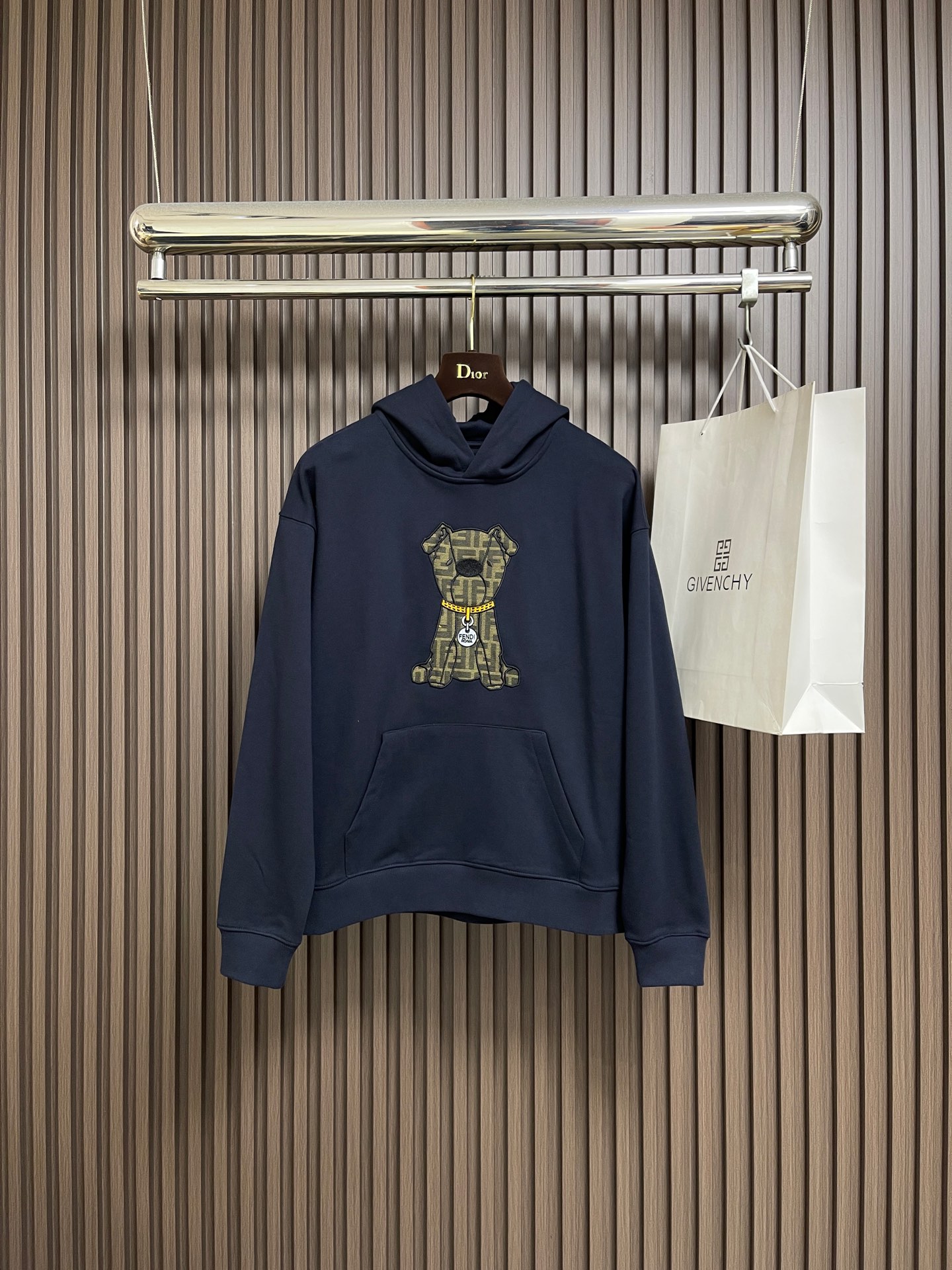 NO:646852,Fendi  The bear embroidered hooded sweatshirt uses a composite structure of 26S double yarn + 10S fish scale bottom. The heavy weight gives the clothing a sculpture-like crispness. The fish scale bottom weave forms a unique concave and convex texture, and after brushing treatment, it appears as skin-friendly as cloud velvet.  Tactile feel. The cuffs and hem are equipped with 21S double yarn 1x1 thread. The ultra-high weight ensures the super elasticity and deformation resistance of the closing area. Innovative use of jacquard weaving + appliqué embroidery + needle embroidery triple process first uses jacquard technology to FF  The pattern is integrated with the brown base fabric; then the main visual hierarchy is built through appliqué positioning; and finally, the edge is precision-wrapped with 16 stitches per inch to realize the seamless integration of the decorative body and the body. The edge strength is increased and the clarity of the pattern outline is enhanced. The loose tailoring of the dropped shoulders breaks through the limitations of the traditional shoulder line and creates a lazy street silhouette.  .The hooded design is matched with the front chest pocket to enhance practical functional attributes. All seams are reinforced with open stitching to ensure that the heavy fabric maintains structural stability during dynamic wear. Sizes XS-L, fendi, hoodie, sweatshirts, hats, alexander  wang19860909Fendi 小熊刺绣连帽卫衣,采用26S双纱＋10S鱼鳞底复合结构,重磅克重赋予衣物雕塑般挺括感.鱼鳞状底层织法形成独特凹凸肌理,经磨毛处理后呈现云绒般亲肤触感.袖口及下摆搭配21S双纱1x1螺纹,超高克重确保收口部位超强回弹性与抗变形能力.创新运用提花织造＋贴布绣＋挨针绣三重工艺先以提花技术将FF 图案与棕色基底织为一体；再通过贴布绣定位构建主视觉层次；最后以每英寸16针的挨针绣精密包边,实现装饰体与衣身的无缝融合,边缘强度提升同时强化图案轮廓的清晰度.落肩宽松剪裁突破传统肩线限制,营造慵懒的街头廓形.连帽设计配合前胸口袋,强化实用机能属性.所有接缝处采用明线锁边加固工艺,确保重磅面料在动态穿着中保持结构稳定.尺码XS-L,,fendi,hoodie,sweatshirts,hats,alexander wang,Men's clothing