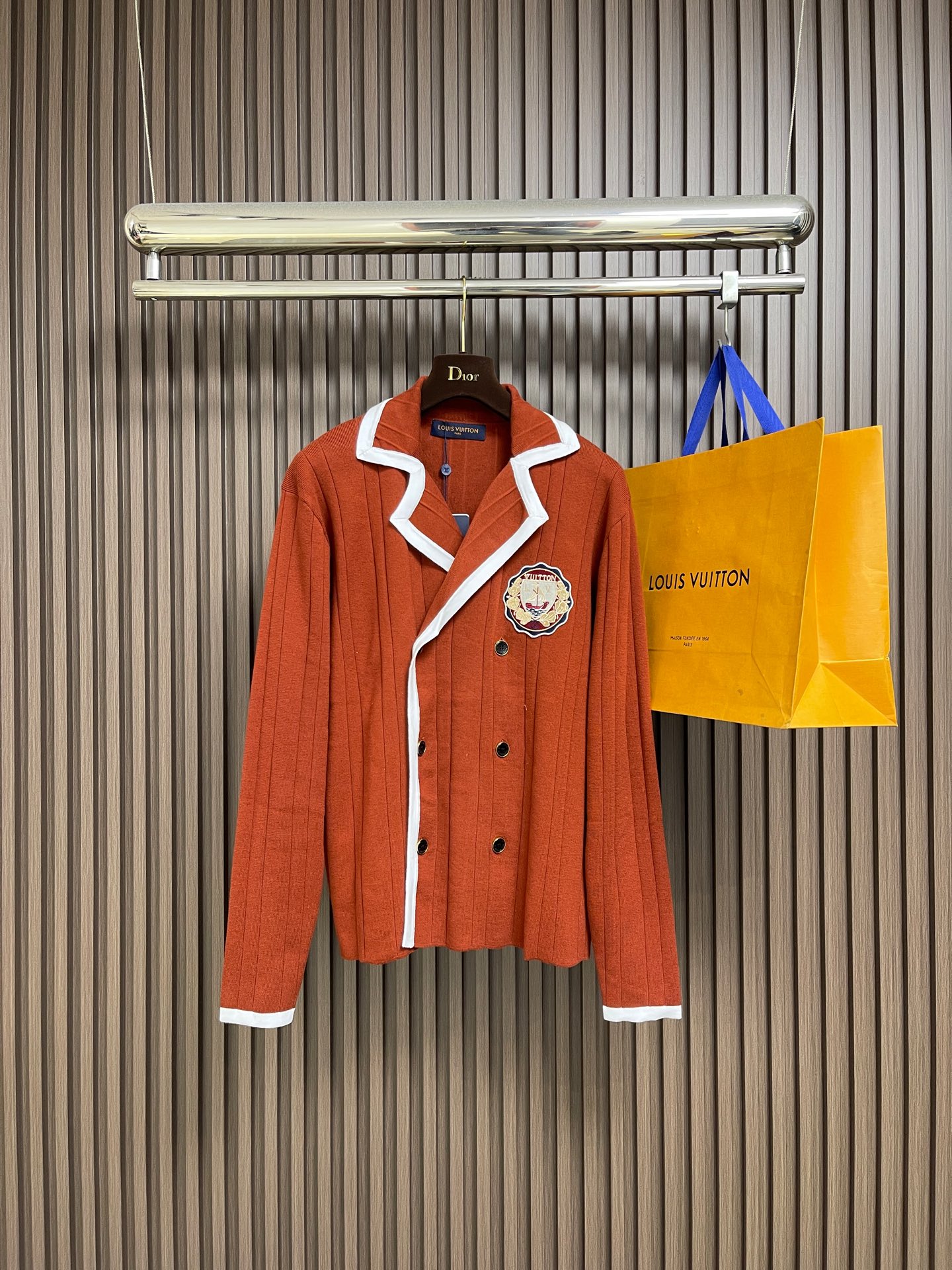 NO:660971,LV  College-style knitted cardigan sweater. This Louis Vuitton knitted cardigan is made of high-count wool blended fabric. It uses vertical pit knitting technology to create a delicate and crisp texture, which combines softness and silhouette support. The collar, placket and cuffs use contrasting piping technology, with white webbing and caramel brown main body to form a visual hierarchy. The edges are reinforced with overlocking to improve wearability. The double-breasted design of the front is made of metal.  The resin buckle echoes the three-dimensional badge on the body - the badge uses embroidery + patching composite technology to precisely sew the brand logo and decorative elements. The color transition is natural and not easy to go off-line. The overall pattern is optimized through side seam diagonal splicing, which not only retains the looseness of knitting, but also strengthens the sharpness of the lines. It is a combination of craftsmanship and design. The overall wiring is straight and delicate, the fabric is comfortable and soft, and the colors are consistent and without color difference.  It can be matched with the same style to create a fashionable look, and can be used in various occasions. Customized accessories, complete with three standards, same style for men and women!  Size S-XL,,louis vuitton,louis vuitton,sweaters, 19860909LV 学院风针织开衫毛衣,这件路易威登针织开衫采用高支数羊毛混纺面料,通过竖坑条针织工艺打造出细腻挺括的肌理感,兼具柔软度与廓形支撑力.领口、门襟及袖口采用撞色滚边工艺,以白色织带与焦糖棕主体形成视觉层次,边缘经锁边加固处理,提升耐穿性.前襟的双排扣设计选用金属质感树脂扣,与衣身的立体徽章相呼应﹣﹣徽章采用刺绣＋贴布复合工艺,将品牌标识与装饰元素精密缝合,色彩过渡自然且不易脱线.整体版型通过侧缝斜向拼接优化剪裁,既保留针织的松弛感,又强化了线条利落度,是工艺与设计感的结合.整体走线平直细腻,面料舒适柔软,颜色一致无色差 能与同款搭配营造时尚造型,驾驭各种场合,定制辅料,三标齐全,男女同款！尺码S-XL,,louis vuitton,louis vuitton,sweaters, ,Men's clothing