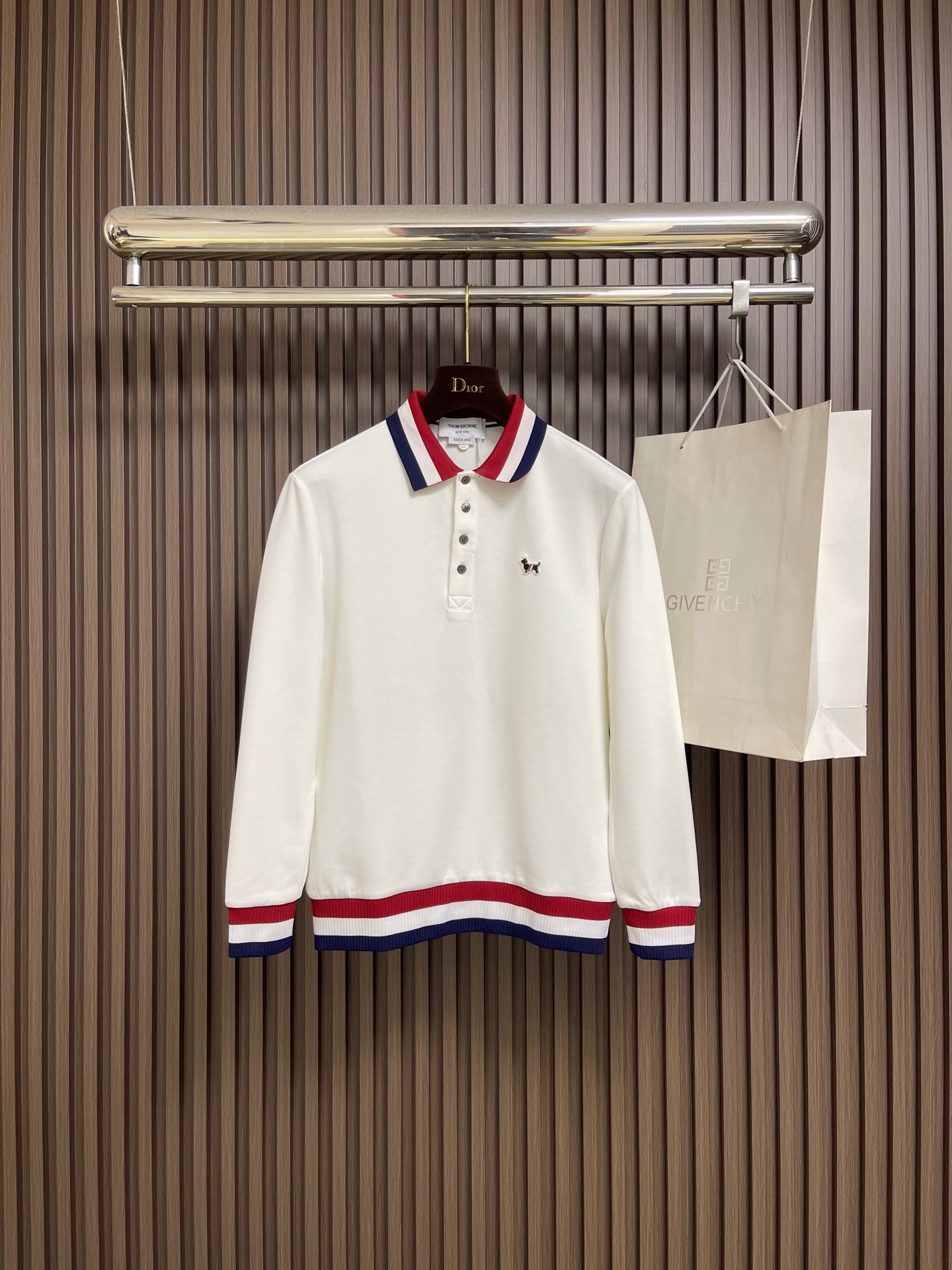 NO:683102,Thom Browne.TB  2025FW new autumn and winter classic long-sleeved POLO shirt with contrasting colors. The red, white and blue contrasting webbing outlines the iconic college style. Customized high-density combed cotton is selected, with fine fibers and excellent wrinkle resistance. The upper body is light and draped without being tight, which perfectly meets the strict requirements of luxury brands for fabrics. Label  The iconic red, white and blue webbing is the core of the vision, the blended ribbing on the collar will not loosen after long wear, the hand-polished shell buttons have a warm luster, and the metal dachshund badge becomes the finishing touch of the style; the hidden brand embroidery stitches are fine, revealing extraordinary taste in a low-key manner. Size M-3XL,,19860909Thom Browne.TB 2025FW秋冬新品经典撞色长袖POLO衫.红白蓝撞色织带勾勒出标志性学院风.选用定制高密精梳棉,纤维细腻且抗皱性出色,上身轻盈垂坠不紧绷,完美契合奢牌对面料的严苛要求.标志性红白蓝织带是视觉核心,领口混纺罗纹久穿不松垮,手工打磨的贝壳纽扣光泽温润,金属腊肠狗徽章则成为造型点睛之笔；隐藏式品牌刺绣针脚细密,低调中流露不凡品味.尺码M-3XL,,,Men's clothing