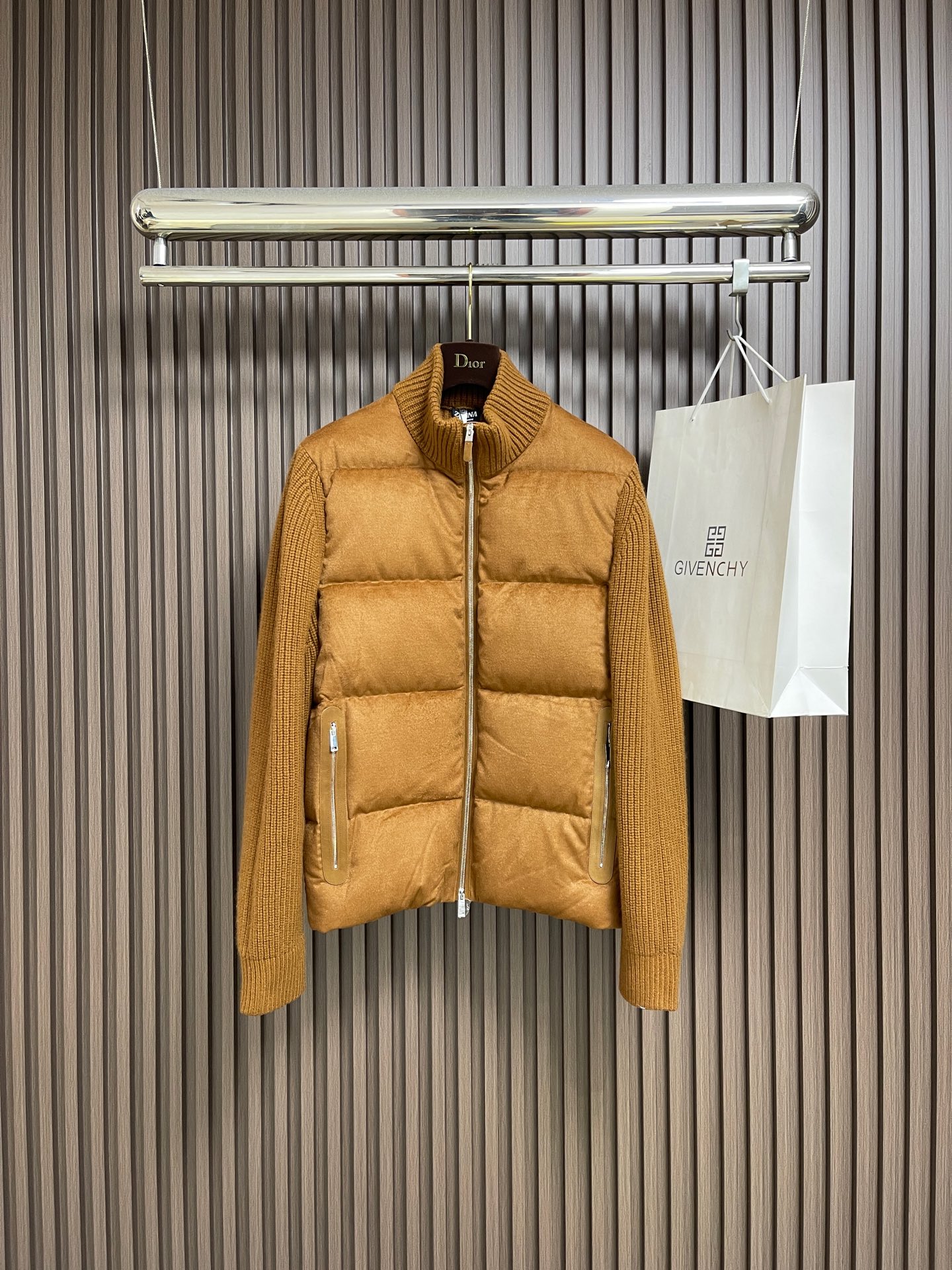 NO:683121,Zegna  The blended woolen splicing knitted down jacket creates a neat and crisp silhouette; while the sleeves are cleverly seamed with soft knitted fabrics, forming a subtle contrast in visual and tactile sense, breaking the conventional single impression and highlighting the sense of high-end layering. The style design is simple and elegant. The classic stand-up collar and smooth zipper running through it outline the dry look.  The lines are refined. The diagonal pockets on both sides are embellished with trim strips of the same color, revealing exquisite details. The interior is filled with 90% high-quality white duck down, combined with the natural texture of wool blended fabrics, ensuring moderate warmth with a light body feel, making it an ideal choice for cold weather. Sizes 46-52, jackets  & coats,down jacket,19860909Zegna 混纺毛呢拼接针织羽绒外套,构筑利落挺括的廓形；而衣袖则巧妙地接缝柔软针织面料,在视觉与触感上形成精妙对比,打破了常规的单一印象,彰显高级层次感.款式设计简约而考究.经典的立领与贯穿的顺滑拉链,勾勒出干练线条.两侧斜插口袋以同色系饰条点缀,于细节处流露精致.其内在填充90％高品质白鸭绒,结合羊毛混纺面料的天然肌理,确保了轻盈体感下的适度保暖性,是应对微寒天气的理想选择.尺码46-52,,jackets & coats,down jacket,,Men's clothing