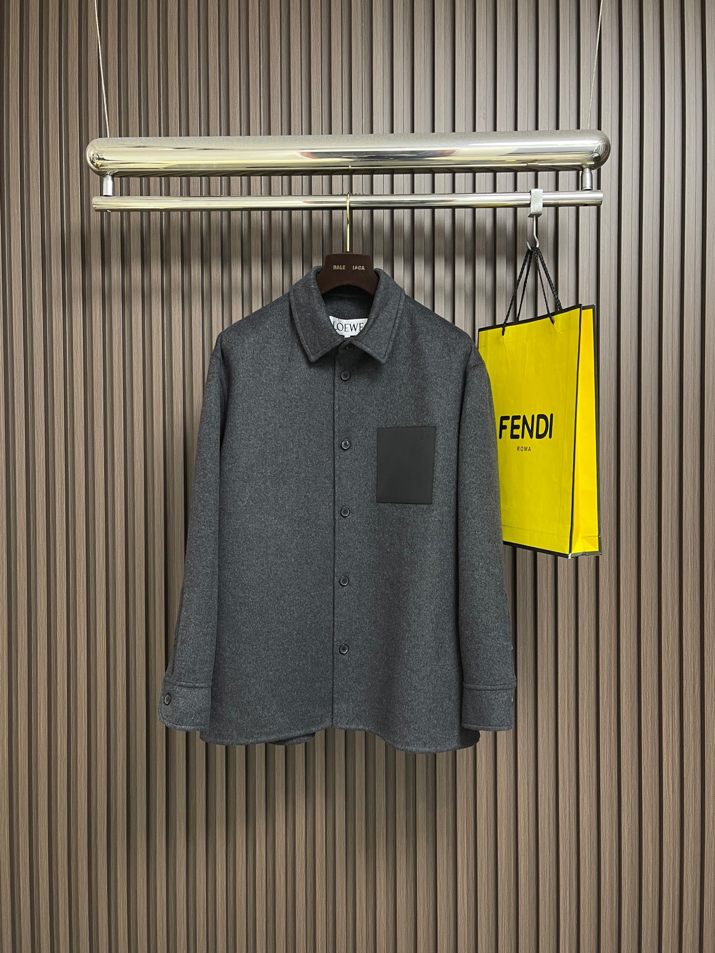 NO:735353,LOEWE  Shirt-style woolen jacket, the fabric is a double-faced woolen jacket with both warmth and breathability. The wool fibers are screened to retain only fine wool with uniform length and excellent toughness, giving the fabric a crisp silhouette and natural wrinkle resistance; improving the overall touch, the suede is as fine as clouds, achieving a 'light and warm' wearing experience. Special textile techniques are used to interweave wool and cashmere fibers to form a subtle two-color texture, which eliminates the need for linings.  The fabric structure is precisely controlled at about 280g per square meter to ensure that it does not appear bulky when worn alone, and can withstand the cool weather when worn alone. The process adopts the traditional double-sided sewing process and is operated by more than experienced seamstresses. There are no exposed stitches on the body of the garment, and the two layers of fabrics are accurately fitted through blind stitching techniques. The stitch density is controlled at 3-4 stitches per centimeter to ensure that the edges are smooth and compliant while retaining the natural drape of the fabric.  It not only improves the durability, but also gives the jacket a minimalist and high-end look visually. The leather patch pocket on the chest is made of vegetable-tanned calfskin, which is dyed with vegetable tannins to give a matte black deep texture. The leather is precisely cut into a square shape with uniform specifications, and then hand-positioned and sewn to the body to ensure the tension balance with the wool fabric and avoid deformation after long-term wear. The Anagram embossing on the bag uses a 0.3mm depth steel mold hot pressing process.  A clear three-dimensional brand logo is formed on the leather surface, and each edge of the pattern has been calibrated repeatedly to ensure smooth lines and low-key recognition. Behind the regular version is millimeter-level size control, and the collar angle is set to 85°, which not only retains the crispness of the shirt but also avoids neck jamming; the shoulder width is 2cm longer than the standard version, taking into account comfort and a lazy and casual atmosphere. Sizes 46-52, loewe, jackets  & coats,jackets & coats,shirts,cowhide,19860909LOEWE 衬衫式羊毛呢夹克外套,面料选择兼具温度与呼吸感的双面呢外套.羊毛纤维经筛选仅保留长度均匀、韧性卓越的细支羊毛,赋予面料挺括廓形与天然抗皱性；提升整体触感,绒面细腻如云朵,实现「轻盈保暖」的穿着体验.通过特殊纺织技法使羊毛与羊绒纤维交织融合,形成正反双色的微妙肌理,既省去内衬的束缚,又让衣身更显利落.这种面料结构,每平方米克重精准控制在280g左右,确保叠穿不显臃肿,单穿亦能抵御微凉气候.工艺采用传统双面呢缝制工艺,由经验超过缝纫师操作.衣身无外露缝线,通过暗缝技法将两层面料精准贴合,针脚密度控制在每厘米3-4针,确保边缘平整服帖,同时保留面料自然的垂坠感.不仅提升耐穿度,更让外套在视觉上呈现极简高级感.胸前皮革贴袋选用植鞣小牛皮,经植物单宁浸染后呈现哑光黑的深质感.皮革精准裁剪统一规格的方正形态,再通过手工定位缝制于衣身,确保与羊毛面料的张力平衡,避免长期穿着后变形.袋面的Anagram压纹采用0.3mm深度的钢模热压工艺,在皮革表面形成清晰立体的品牌标识,每一个处图案边缘都经过反复校准,确保线条流畅,低调中体现辨识度.常规版型的背后是毫米级的尺寸把控衣领角度设定为85°,既保留衬衫式的利落,又避免卡颈；肩宽比标准版型增加2cm,兼顾舒适度与慵懒随性的氛围.尺码46-52,,loewe,jackets & coats,jackets & coats,shirts,cowhide,,Men's clothing