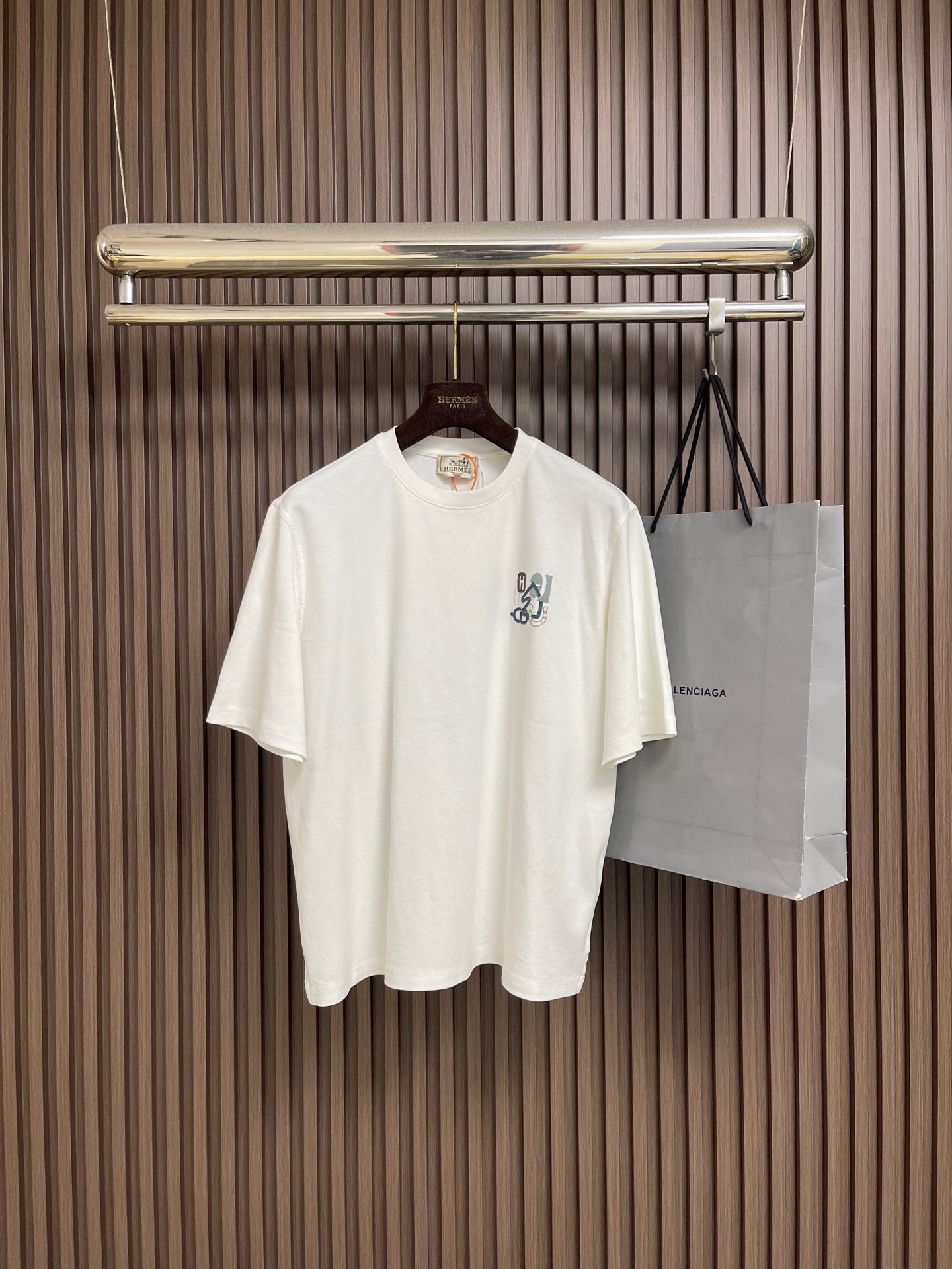 NO:745873,Hermes Paris patch leather short-sleeved T-shirt, custom-made double-sided Austrian cotton worsted fabric, delicate, soft and comfortable against the skin, with high-end matte gray as the main tone, with an effortless sense of luxury. The three-dimensional saddle leather logo is embellished on the chest, derived from the natural drape of the stirrup belt. It is the status code of the invisible noble. It trembles with the pace. Like the smart rhythm of the harness on the riding body, it injects breathing and vitality into the short sleeves. True nobility is not about showing off, but about inheriting.  Reshaping the implicit luxury of street aristocrats with a century-old harness gene as the soul. Leather art relief embroidery. Priority is given to 3D modeling to simulate patterns and precise pattern making. Then the leather is decomposed and shaped. Finally, an imported Behringer embroidery machine is used to position and lock the edges. The lines are smooth and delicate, and the fabrics have been washed. They have a better hand feel and texture. They are not easy to deform, shrink or fade.  Maintain long-term beauty. The overall wiring is straight and delicate, the fabric is comfortable and soft, and the color is consistent without color difference. It can be matched with the same style to create a fashionable look and control various occasions. Customized accessories, complete with three standards, same style for men and women!  Size S-XL S size bust 114 shoulder width 46 length 67 medium size bust 118 shoulder width 47.5 length 69 L size bust 122 shoulder width 49 length 71 XL size bust 126 shoulder width 50.5 length 73, hermes, T-shirt, tees, t-shirt,19860909Hermes Paris 贴饰皮革短袖T恤,定制双面奥棉精纺纱面料 细腻柔软舒适贴肤 以高级雾面灰为主基调 自带不费力的高级感 马鞍皮革的立体徽标点缀于胸前源自马镫皮带的自然垂坠弧度 隐形贵族的身份暗号 随步伐轻颤 像马具在骑土身上的灵动韵律 为短袖注入呼吸感与生命力 真正的贵气 不在张扬 而在传承 以百年马具基因为魂 重塑街头贵族的隐性奢华.皮艺浮雕绣 优先通过3D建模模拟图案精准打版 再将皮革分解塑形 最终用进口机百灵达刺绣机坐边定位锁边 线条流畅而细腻,面料都经过浇洗 手感质感更佳 不易变形 不易缩水 不易褪色 保持长久的美观.整体走线平直细腻,面料舒适柔软,颜色一致无色差能与同款搭配营造时尚造型,驾驭各种场合,定制辅料,三标齐全,男女同款！尺码S-XL S码胸围114 肩宽46 衣长67 M码 胸围118 肩宽47.5衣长69 L码胸围122 肩宽49 衣长71 XL码 胸围126 肩宽50.5衣长73,,hermes,T-shirt,tees，t-shirt,,Men's clothing