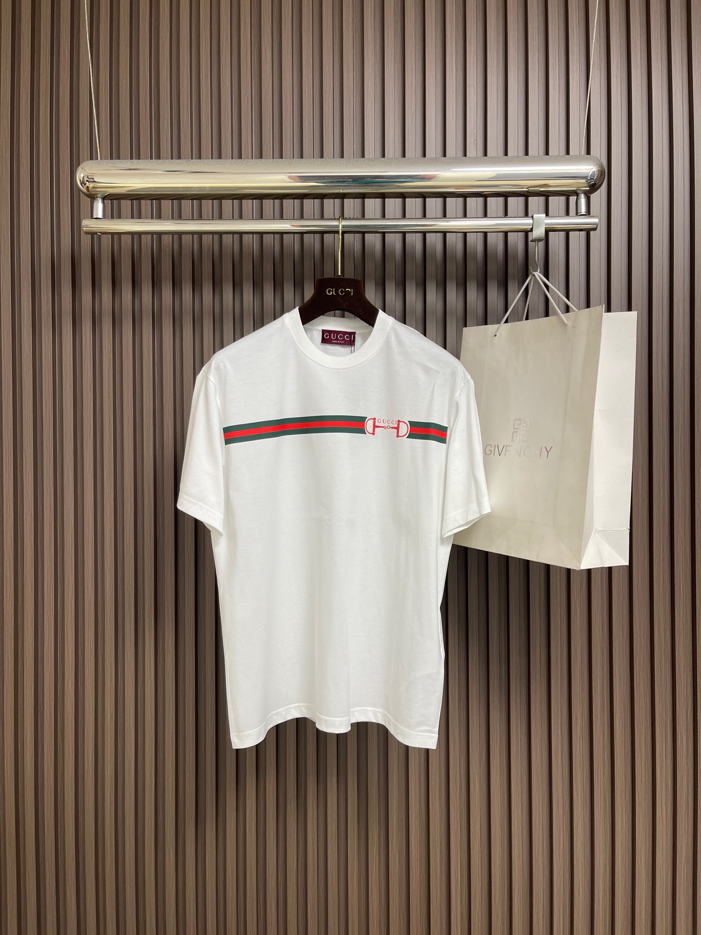 NO:759346,Gucci web lock round neck short-sleeved T-shirt, specific mercerized long-staple cotton fabric, made of 50S double-strand mercerized cotton, weight 165gm2; matched with 32S  1x1 tensioner thread, 300gm2. The high count of the fabric ensures that the yarn is extremely fine, giving the fabric a silky and delicate touch; double-twisting greatly improves the yarn strength and pilling resistance, solving the shortcomings of high-count yarns that are easy to be fragile; the fabrics made are usually softer, smoother and finer. Mercerization. The cotton fiber is permanently glossed through alkali solution, making the fabric appear silk-like.  luster, while enhancing fiber strength, dye adsorption and dimensional stability. Webbing lock glue printing, environmentally friendly elastic glue suede printing is a composite process that combines elastic coating and velvety texture. It first transfers the environmentally friendly elastic glue to the fabric through a high mesh screen to form a flexible base with excellent stretchability; special velvet powder is implanted on the surface of the incompletely cured glue layer for velvet pressing  After precise temperature control and curing, a decorative layer integrating matte suede texture and elastic coating is formed. The pattern area has the stretch-resistant and anti-cracking properties of elastic glue and the delicate touch and matte vision of suede. The touch is soft and plump without hardening. The suede texture can be accurately presented with the printing shape, the color is saturated and full of three-dimensional layers, and it has both decorative beauty and wearing comfort. Simple  Approximately vertical round neck short-sleeved version, standard straight cut creates a simple and modern silhouette through the three-dimensional shoulder line and vertical body proportions. The back collar adopts triple anti-deformation technology with built-in memory inserts, ultrasonic fit interlining and double-needle four-thread reinforced sewing. The hem and cuffs are edged with special-purpose machine-made open stitching, and the seam tension is precisely calibrated to ensure that it remains flat after multiple washes. Sizes XS-L  XS size, shoulder width 48, chest size 106, length 69, size S, size shoulder width 49.5 size, chest size 110, length 71 size M, size shoulder width 51, size chest 114 size, length 73 size L, size shoulder width 52.5, chest size 118 size, length 75, gucci, T-shirt, tees, t-shirt, real silk,19860909Gucci 织带锁扣圆领短袖T恤,特定丝光长绒棉面料,采用50S双股丝光棉,克重165gm2；搭配32S 1x1拉架螺纹,300gm2.面料高支数确保纱线极细,赋予织物丝绸般的细腻触感；双股捻合则大幅提升纱线强度与抗起球性,解决了高支纱易脆弱的缺点；制成的面料通常越柔软、光滑且精细.丝光处理.通过碱液对棉纤维进行永久性光泽整理,使面料呈现真丝样光泽,同时增强纤维强度、染料吸附力与尺寸稳定性.织带锁扣胶浆印花,环保弹力胶浆绒面印花是一种结合弹性涂层与绒感肌理的复合工艺.其先通过高目数网版将环保弹力胶浆转印至面料,形成具备优异拉伸性的柔韧基底；在未完全固化的胶浆层表面植入特制绒粉进行压绒处理,经精准控温固化后,形成哑光绒面质感与弹性涂层一体化的装饰层.图案区域同时具备弹力胶浆的耐拉伸、抗开裂特性与绒面的细腻触感和哑光视觉,触感柔软丰盈无硬化感.绒面纹理可随印花形状精确呈现,色彩饱和且富有立体层次,兼具装饰美观与穿着舒适度.简约垂直圆领短袖版型,标准直筒剪裁通过立体肩线与垂直衣身比例,营造简约现代轮廓.后领采用三重防变形工艺内置记忆嵌条、超声波贴合衬布与双针四线加固缝制.下摆及袖口以专机坎车明线收边,缝线张力经过精密校准,确保多次洗涤后仍保持平整形态.尺码XS-L XS码肩宽48 胸围106 衣长69  S码肩宽49.5 胸围110衣长71  M码 肩宽51胸围114衣长73 L码 肩宽52.5胸围118衣长75,,gucci,T-shirt,tees，t-shirt,real silk,,Men's clothing