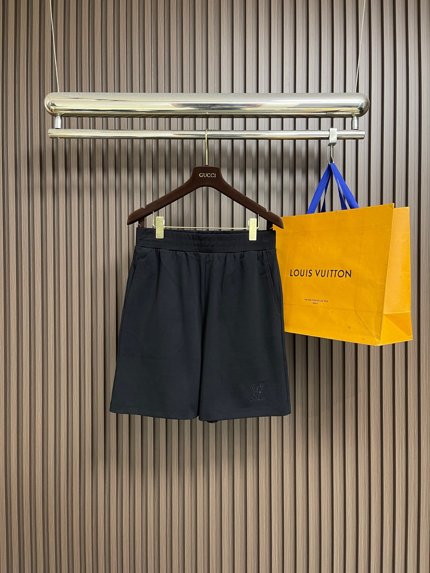 NO:759407,Short sleeve shorts LV  2026ss new summer decorative knitted short-sleeved T-shirt shorts suit. This black mid-sleeve top is made of high-count combed cotton blended fabric. It has been preshrunk and brushed. It feels soft and skin-friendly and has a good drape. It will not change easily after long-term wear.  The shape is pilling. The round neck uses double-strand hemming technology and is matched with ribbing of the same color, which fits the neck line and is not easy to loose. The body is cut with dropped shoulders, and the three-quarter sleeves are designed to modify the arm lines. The hem and cuffs are ribbed with the same fabric.  It is tightened to enhance wearing stability. The brand logo is presented with hollow embroidery technology on the left chest. The stitches are fine and even, three-dimensional and full of exquisite texture. The whole body is combined with flat stitching and seamless gluing technology to reduce seam friction and improve wearing comfort, taking into account both daily leisure and light business scenes. The version is loose and accommodates various body shapes, durable and easy to care for, highlighting a low-key luxury texture. The overall wiring is straight and delicate, the fabric is comfortable and soft, and the color is consistent and has no color difference.  It can be matched with the same style to create a fashionable look, and can be used in various occasions. Customized accessories, complete with three standards, same style for men and women!  ,,louis vuitton,shorts,T-shirt,tees,t-shirt,19860909短袖 短裤 LV 2026ss夏季新款装饰针织短袖T恤短裤套装,这件黑色中袖上衣采用高支精梳棉混纺面料,经预缩与磨毛处理,触感柔软亲肤且具备良好垂坠感,久穿不易变形起球.圆领采用双股线包边工艺,搭配同色系罗纹收边,贴合颈部线条且不易松垮.衣身采用落肩剪裁,七分袖设计修饰手臂线条,下摆与袖口均使用同面料罗纹收束,增强穿着稳定性.左胸位置以镂空刺绣工艺呈现品牌标识,针脚细密均匀,层次立体且富有精致质感.整体采用平车锁边与无痕压胶工艺结合,减少缝线摩擦感,提升穿着舒适度,兼顾日常休闲与轻商务场景,版型宽松包容各种身形,耐穿易打理,彰显低调奢华质感.整体走线平直细腻,面料舒适柔软,颜色一致无色差 能与同款搭配营造时尚造型,驾驭各种场合,定制辅料,三标齐全,男女同款！,,louis vuitton,shorts,T-shirt,tees，t-shirt,,Men's clothing