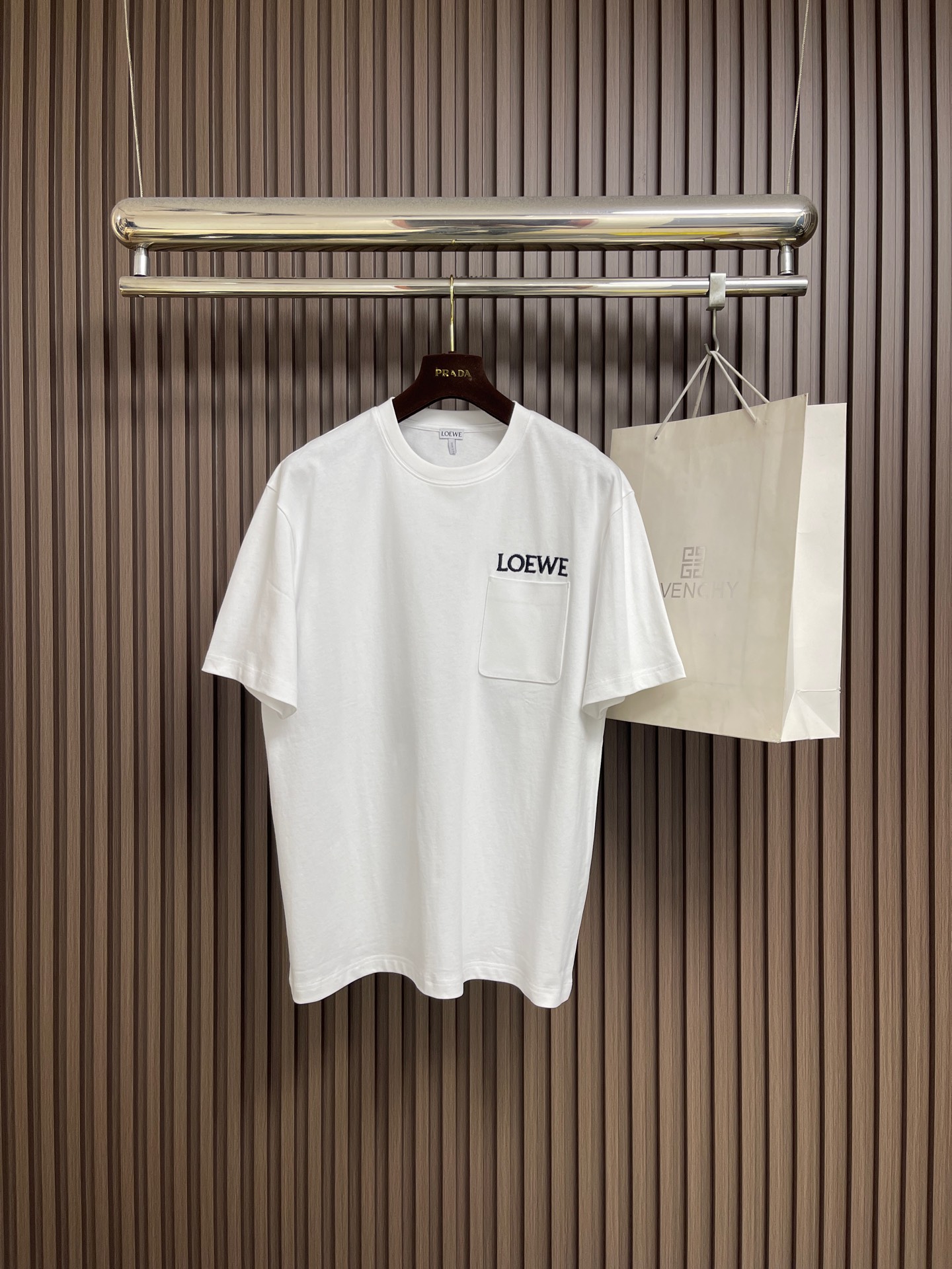 NO:759365,LOEWE  The pocket logo embroidered round neck short-sleeved T-shirt is made of the original pure cotton material. The clothes are thick, crisp, drapey, and not easy to collapse and deform. The double yarn structure makes it more durable and washable, and not easy to deform. It has a delicate touch that is far superior to ordinary cotton T-shirts on the market. The pocket logo embroidery is the core logo of LOEWE. The embroidery process requires extremely high thread materials, stitch density and pattern restoration, and is of high quality.  The key point is that the thread weight of 320g customized threaded cuffs and collar is even higher than that of the main fabric (320g), which ensures the long-term stability of the collar and sleeve shapes and is not easy to loosen after washing. It is custom-woven and dyed, without any color difference from the original version. The ingenious craftsmanship is perfectly restored, three standards are complete, and customized accessories. Sizes S-XL, loewe, T-shirt, tees, t-shirt,19860909LOEWE 口袋logo刺绣圆领短袖T恤,面料采用原版一致纯棉材质,衣服厚实、挺括、有垂感,不易软塌变形.双纱结构使其更耐穿耐洗,不易变形.触感细腻,远超市面普通棉T.口袋logo刺绣LOEWE的核心标识,刺绣工艺对线材、针脚密度和图案还原度要求极高,是品质的关键.320g定制螺纹袖口、领口的螺纹克重甚至比主面料还高（320g),确保了领型和袖型的长期稳定,洗后不易松懈.定织定染,与原版无任何色差.匠心工艺完美还原,三标齐全,定制辅料.尺码S-XL,,loewe,T-shirt,tees，t-shirt,,Men's clothing