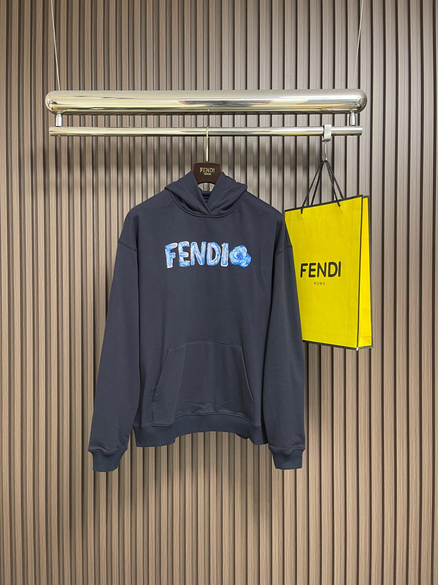 NO:759320,FENDI  The hooded sweatshirt with embroidery is made of single-sided fish-scale fabric woven with cotton as the base. The front is a smooth knitted surface, and the skin-contacting surface is formed into three-dimensional terry through the floating knitting technology of the knitting machine, which increases the fluffiness and delicate touch. The terry structure absorbs large amounts of water and evaporates quickly. After pre-shrinking treatment, the shrinkage rate is less than 2, ensuring the stability of the size of the garment. The dark blue dyeing and finishing uses reactive dyes, the color is rich and full, and it is not easy to fade after repeated washing. 'Fd' on the chest  Flower' pattern is precision embroidered by Japanese Tajima embroidery machine, integrating multi-color gradient and three-dimensional texture to present a unique watercolor effect. Letters and flower patterns use different shades of blue and white gradient embroidery thread, with a natural transition from light blue to indigo, simulating the layering of watercolor blooming. The fineness of each embroidery thread is 4  0S2, through high-density embroidery of 1,200 stitches, ensures even fusion of colors without obvious color block boundaries. The center of the flower forms a full three-dimensional texture through the stacking of yarns, simulating the soft visual sense of petals. The edges are outlined with flat embroidery, with stitches as fine as hair, and smooth and natural lines.  .The edges of the letters are embroidered with 'virtual and solid needles', and some areas are left blank to create the 'flying white' effect of watercolor paintings and enhance the flexibility of the pattern. The kangaroo pocket on the chest is made of twill cotton material. The edge of the bag is folded in 1cm and then double-stitched with topstitching. The stitch spacing is 0.3cm to ensure that the bag shape is three-dimensional and crisp. It can accommodate anything  It is a body-worn item that combines practicality and decoration. The cuffs and hem are all made of 1x1 rib of the same color. The raw material is 97% cotton + 3% spandex blend. The thickness is 2.5mm. It has excellent resilience and fits the wrist and waist closely to prevent cold wind from entering while maintaining the neat outline of the sweatshirt. Sizes S-XL  Size S, shoulder width 57, bust 118, size M, shoulder width 58, bust 122, size L, shoulder width 59, bust 126, size L, shoulder width 59, bust 126, size XL, shoulder width 60, bust 130, length 70,,fendi,hoodie,sweatshirts,hats,19860909FENDI 饰刺绣连帽卫衣,选用棉为基底编织而成的单面鱼鳞布面料,正面为平滑的针织面,触肤面通过针织机的浮线编织技术形成立体的毛圈,增加蓬松感,同时触感细腻.毛圈结构吸水量大且蒸发快,经过预缩处理之后,缩水率低于2,确保成衣尺寸稳定.深蓝色染整采用活性染料,色泽浓郁饱满,多次洗涤不易褪色.胸前'Fd Flower'图案采用日本田岛绣花机精密刺绣,融合多色渐变与立体肌理,呈现独特的水彩效果.字母与花朵图案使用不同深浅的蓝白渐变绣线,从浅蓝到靛蓝自然过渡,模拟水彩晕染的层次感.每根绣线细度为40S2,通过1200针英寸的高密度刺绣,确保色彩均匀融合,无明显色块边界,花朵中心处通过纱线的堆叠形成饱满的立体肌理,模拟花瓣的柔软视觉感官.边缘则以平绣勾勒轮廓,针脚细密如发丝,线条流畅自然.字母边缘采用'虚实针'刺绣,部分区域留白,营造水彩画的'飞白'效果,增强图案的灵动性.胸前袋鼠口袋采用斜纹棉料,袋口边缘内折1cm后双线辑明线,线迹间距0.3cm,确保袋型立体挺括.可容纳随身物品,兼顾实用性与装饰性.袖口与下摆均采用同色系1x1罗纹,原料为97％棉＋3％氨纶混纺,厚度达2.5mm,回弹性优异,紧密贴合手腕与腰部,防止冷风灌入,同时保持卫衣的利落轮廓.尺码S-XL S码肩宽57胸围118 衣长67 M码 肩宽58胸围122 衣长68 L码肩宽59胸围126 衣长69 XL码 肩宽60胸围130 衣长70,,fendi,hoodie,sweatshirts,hats,,Men's clothing