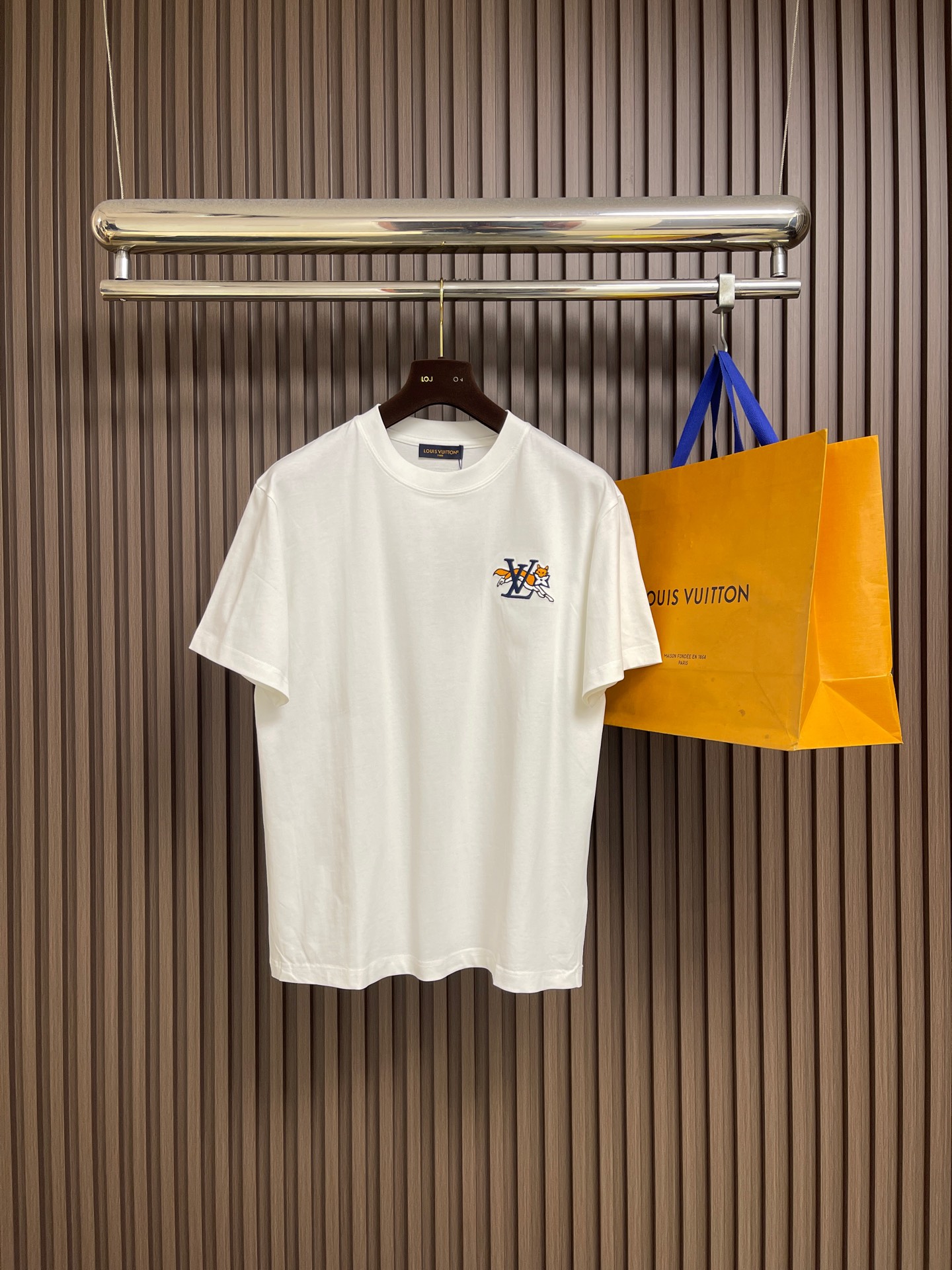 NO:759353,LV 2026FW early spring new short-sleeved T-shirt. This cotton short-sleeved T-shirt draws inspiration from the UK and presents the playful 1V Lovers logo and a fox holding a Monogram flower. The back is embellished with Marque 1.Vuitton Deposee embroidered patches. Made of heavy cotton fabric, it adds a sense of sophistication to the casual look. Sizes M-3XL M size length 67cm shoulder width 47.5cm  Bust 104cm Length 69cm Shoulder width 49cm Bust 108cm XL length 71cm Shoulder width 50.5cm Bust 112cm XXL length 73cm Shoulder width 52cm Bust 116cm19860909LV 2026FW早春新款短袖T恤,这款棉质短袖T恤,从英国汲取灵感,呈现了俏皮的 1V Lovers标识和一只叼着 Monogram 花卉的狐狸.后背点缀 Marque 1.Vuitton Deposee 刺绣贴饰.采用重磅棉质面料制成,为休闲造型增添了精致感.尺码M-3XL M码衣长67cm肩宽47.5cm 胸围104cm L码衣长69cm肩宽49cm 胸围108cm XL码衣长71cm 肩宽50.5cm 胸围112cm XXL码衣长73cm肩宽52cm 胸围116cm XXXL码衣长75cm 肩宽53.5cm 胸围120cm,,louis vuitton,versace,T-shirt,tees，t-shirt,,Men's clothing