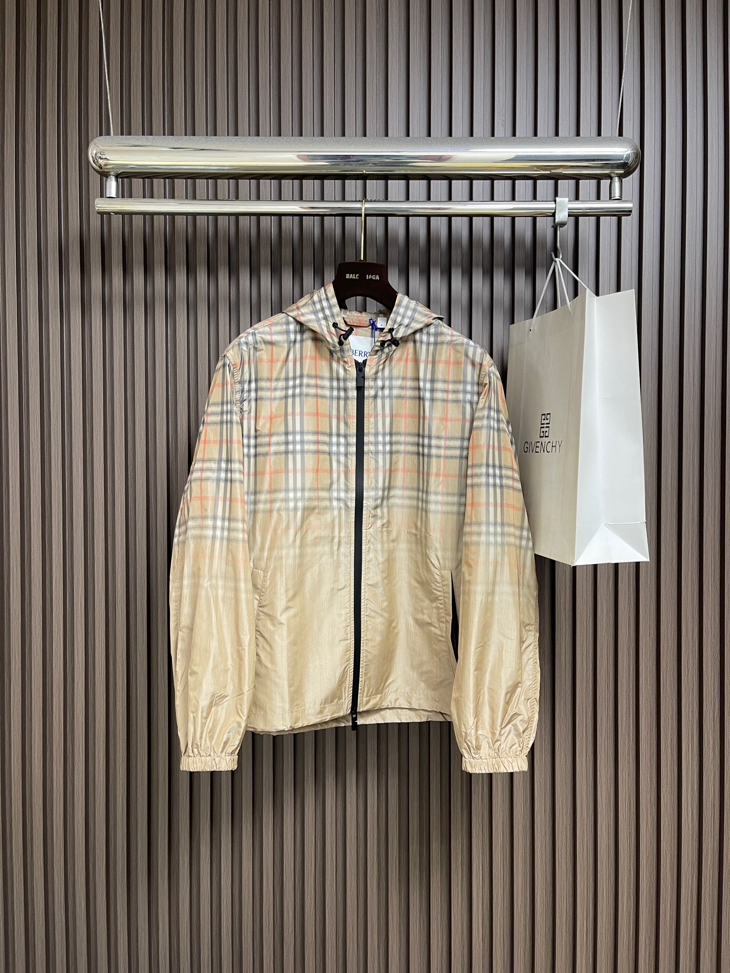 NO:775896,BURBERRY  The plaid gradient hooded jacket is made of a thin nylon blended fabric specially supplied by the brand. It has been treated with a special anti-wrinkle and waterproof coating. The texture is light and burdenless, and it feels smooth and crisp. It also has excellent breathability and windproof performance, ensuring a comfortable wearing experience and full protection of the jacket.  Weather-proof and practical; the neckline adopts a classic hooded design, with a same-color drawstring and metal adjustment buckle, which can be freely adjusted to provide effective protection for the head and add a casual layer to the overall look; the body adopts the iconic Vintage plaid pattern.  The gradient dyeing process naturally transitions from the classic camel, black and red plaid to the pure light khaki hem, breaking the stereotype of the traditional plaid, making it visually rich and highly recognizable; a black matte zipper runs through the front, with zipper pullers of the same color, and the interior is low-key  Converged, there are hidden pockets on both sides, taking into account both beauty and practicality; the shoulder lines are neat and tolerant, and can be worn alone to create a street trend, or as a layered item, which can be easily controlled by all body shapes. Sizes S-XL, burberry, jackets  & coats,jackets & coats,hats,19860909BURBERRY 格纹渐变连帽夹克外套,采用品牌特供的轻薄锦纶混纺面料,经过特殊的抗皱与防水涂层处理,质地轻盈无负担,触感顺滑挺括,同时具备出色的透气性与防风性能,保证了外套的舒适穿着体验与全天候实用性；领口采用经典连帽设计,搭配同色系抽绳与金属调节扣,可自由调节松紧,既能为头部提供有效防护,又能为整体造型增添随性层次；衣身采用标志性的Vintage格纹图案,通过渐变晕染工艺,从经典的驼色、黑色与红色格纹,自然过渡到纯净的浅卡其色下摆,打破传统格纹的刻板印象,视觉层次丰富且极具辨识度；正面采用黑色哑光拉链贯穿,搭配同色系拉链头,低调内敛,两侧设有隐形插袋,兼顾美观与实用性；肩部线条利落,包容性强,既能单穿打造街头潮流感,也可作为叠穿单品,各类身形皆能轻松驾驭.尺码S-XL,,burberry,jackets & coats,jackets & coats,hats,,Men's clothing