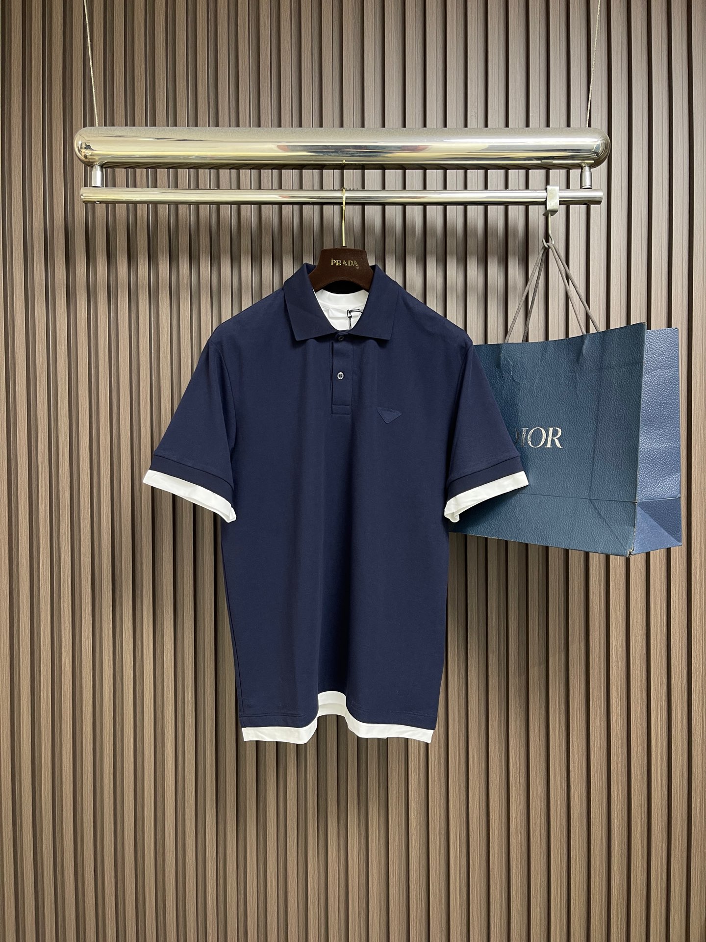 NO:773703,Prada Short-sleeved POLO shirt with contrasting fabric triangle logo, made of pique fabric woven from cotton fiber. The cotton fiber gives the fabric the characteristics of moisture absorption, breathability, and skin-friendliness. The surface of the pique structure has uneven holes, shaped like a honeycomb, which promotes air circulation and has excellent heat dissipation efficiency. Because of the cotton yarn The elasticity is enhanced after pique knitting, and it can still rebound after repeated stretching. The rib knitted neckline is knitted with a double needle bed, so that the coils are alternately looped on the front and back, forming a 1*1 rib with longitudinal concave and convex patterns. The elastic structure makes the neckline fit the neck naturally, avoiding the feeling of restraint, and the double layer The sewing process is linked to the body, which significantly reduces the probability of the neckline expanding into a 'ruffle' and collapsing, and maintains its initial shape for a long time. By actively intervening in the shrinkage potential of cotton fibers, the fabric is achieved from being volatile to being stable, improving dimensional stability while not easily deforming. Pleats. Contrast-colored jersey trim gives a sense of layering and enhances visual beauty. The overall routing is straight and delicate, the fabric is comfortable and soft, and the colors are consistent without color difference. It can be matched with the same style to create a fashionable look, and can be used in various occasions. Customized accessories, complete with three standards, the same style for men and women! Size S-XL S size shoulder width 47 bust 106 Length 71 M size shoulder width 48 bust 110 Length 72 L size shoulder width 49 bust 114 Length 73 XL size shoulder width 50 bust 118 Length 74,, prada, T-shirt,19860909Prada 饰撞色织物三角标短袖POLO衫,选用棉纤维编织而成的珠地布.棉纤维赋予面料吸湿透气,亲肤等特点.珠地结构表面呈现凹凸疏孔,形似蜂巢,促进空气循环,散热效率优良.因棉纱经珠地编织后弹性增强,反复拉伸仍可回弹.罗纹针织领口使用双针床编织,使线圈在正反面交替成圈,形成纵向凹凸纹路的1*1罗纹.弹性结构使领口自然贴合颈,避免束缚感,加之双层缝纫工艺链接衣身,显著降低领口外扩成'荷叶边'的概率与塌陷,保持长久初始形态.通过主动干预棉纤维收缩潜能,实现了面料从易变到稳定的跨越,提升了尺寸稳定性,同时不易变形,褶皱.撞色平纹针织饰边赋予层次感,同时强化视觉美感.整体走线平直细腻,面料舒适柔软,颜色一致无色差能与同款搭配营造时尚造型,驾驭各种场合,定制辅料,三标齐全,男女同款！尺码S-XL S码肩宽47胸围106 衣长71 M码 肩宽48胸围110 衣长72 L码肩宽49胸围114 衣长73 XL码 肩宽50胸围118 衣长74,,prada,T-shirt,,Men's clothing