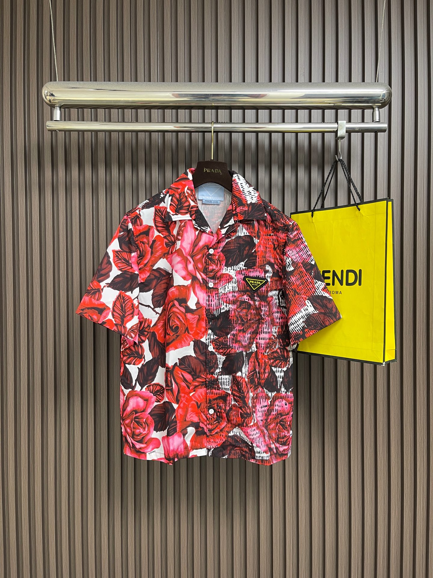 NO:827499,PRADA  The rose print triangle logo short-sleeved shirt is made of imported high-count cotton blended fabrics. It has been treated with mercerized pre-shrinking technology. It feels smooth and skin-friendly, has excellent breathability and drape. The upper body is light and comfortable, and will not be easily deformed after long-term wear. It always maintains a smooth and neat silhouette. The body of the shirt adopts the brand's exclusive rose print design, with a strong red and black rose pattern and a textured background. The print uses environmentally friendly active digital direct injection technology, with rich colors.  It is bright and bright, with natural layer transitions, clear and delicate patterns, and is not easy to fade and crack; the brand's iconic metal triangle logo is inlaid on the left chest and is made with three-dimensional embossing technology, low-key highlighting the brand recognition; the cuffs are made of flat-stitched hemming technology, with flat and smooth edges without excess threads; the hem is straight-cut, with a loose and comfortable fit, which is not flattering on the body shape and takes into account the practicality and style of daily wear. Sizes S-XL  Size S, shoulder width 48.8, bust 112, length 68, size M, shoulder width 50, bust 116, length 69.5, size L, shoulder width 51.2, bust 120, length 71, size XL, shoulder width 52.4, bust 124, length 72.5,,prada,shirts,T-shirt,19860909PRADA 玫瑰印花三角标短袖衬衫,甄选进口高支棉混纺面料,经过丝光预缩工艺处理,触感顺滑亲肤,兼具优越的透气性与垂坠感,上身轻盈舒适,久穿不易变形,始终保持平整利落的廓形质感；衣身采用品牌专属玫瑰印花设计,以浓烈的红黑玫瑰图案搭配肌理感背景,印花采用环保活性数码直喷工艺,色彩饱满鲜亮,层次过渡自然,图案清晰细腻,不易掉色开裂；左胸位置镶嵌品牌标志性的金属三角徽标,采用立体压印工艺打造,低调彰显品牌辨识度；袖口采用平缝锁边工艺,边缘平整光滑,无多余线头；衣摆采用直筒剪裁,搭配宽松舒适的版型,不挑身材,兼顾日常穿搭的实用性与造型感.尺码S-XL  S码肩宽48.8 胸围112 衣长68 M码 肩宽50 胸围116 衣长69.5 L码肩宽51.2胸围120 衣长71 XL码 肩宽52.4 胸围124 衣长72.5,,prada,shirts,T-shirt,,Men's clothing