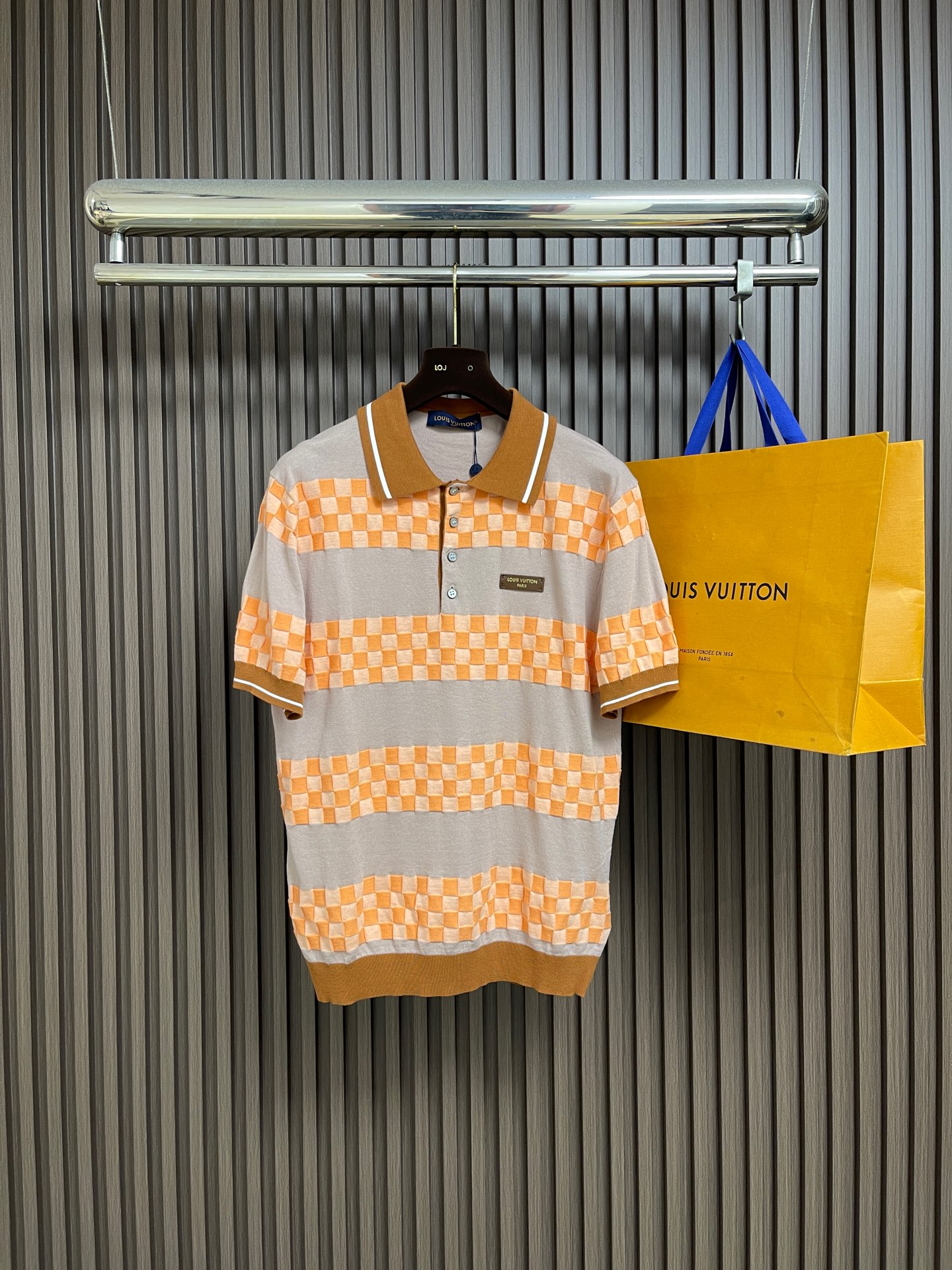 NO:832998,LV  Letter emblem color-blocked striped chess-check jacquard knitted short-sleeved POLO shirt. This letter-emblem color-blocked striped chess-check jacquard knitted short-sleeved POLO shirt is made of fine knitted fabric. It feels soft and skin-friendly, and has good breathability and drape. The body of the shirt is presented with orange and gray contrasting stripes and checker jacquard technology, with distinct layers and rich texture. The letter emblem embellishment on the chest adds to the distinction.  Recognizability. Contrast color ribbed lapels and cuffs are matched with exquisite buttons. The wiring is neat and firm, and the details show quality. The overall fit is loose and comfortable, taking into account both leisure and fashion. It can be worn freely and stylishly in daily life. At the same time, gentle washing and care methods must be followed to avoid high temperature, bleaching and exposure to extend the service life of the clothes. The overall wiring is straight and delicate, the fabric is comfortable and soft, and the color is consistent without color difference.  It can be matched with the same style to create a fashionable look, and can be used in various occasions. Customized accessories, complete with three standards, same style for men and women!  Size S-XL S size bust 108 shoulder width 44 length 69 medium size bust 112 shoulder width 46 length 71 L size bust 116 shoulder width 48 length 73 XL size bust 120 shoulder width 50 length 75,,louis vuitton,T-shirt,19860909LV 字母徽章拼色条纹棋格提花针织POLO衫,这款字母徽章拼色条纹棋格提花针织短袖POLO衫,采用细腻针织面料打造,触感柔软亲肤,兼具良好透气性与垂坠感.衣身以橙灰撞色条纹与棋格提花工艺呈现,层次鲜明且富有质感,胸前字母徽章点缀增添辨识度.撞色罗纹翻领与袖口搭配精致纽扣,走线工整牢固,细节尽显品质.整体版型宽松舒适,兼顾休闲与时尚感,日常穿着自在有型,同时需遵循轻柔洗护方式,避免高温、漂白与暴晒,延长衣物使用寿命.整体走线平直细腻,面料舒适柔软,颜色一致无色差 能与同款搭配营造时尚造型,驾驭各种场合,定制辅料,三标齐全,男女同款！尺码S-XL S码 胸围108 肩宽44衣长69 M码胸围112肩宽46衣长71 L码 胸围116肩宽48衣长73 XL码胸围120 肩宽50 衣长75,,louis vuitton,T-shirt,,Men's clothing