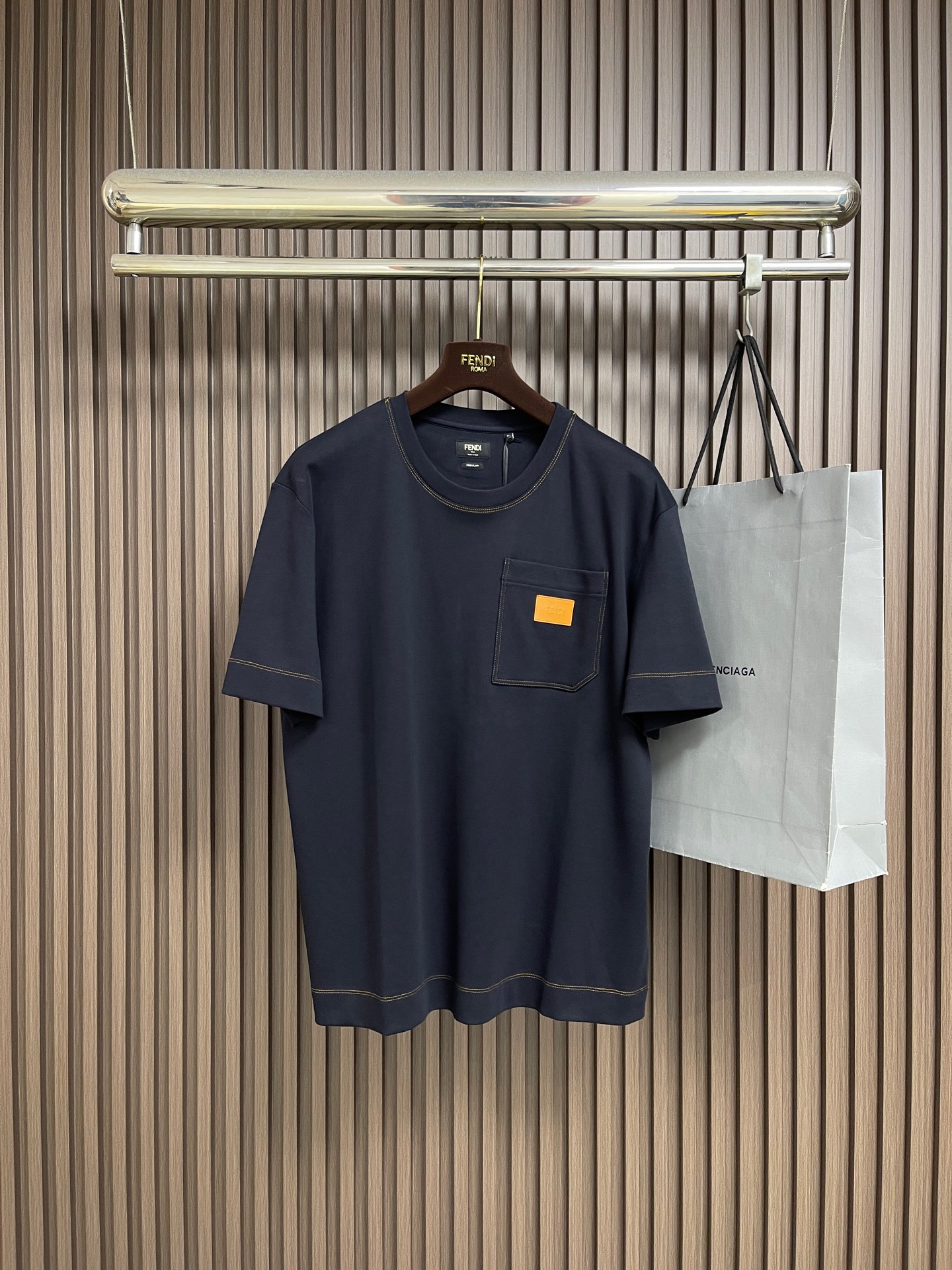 NO:837750,Fendi  Short-sleeved T-shirt with pocket leather label and pocket decoration. It is made of high-count combed cotton. It is made of 280g heavyweight double-ply jersey fabric and has been pre-shrunk and washed. The body adopts an Oversized drop shoulder version. The round neck uses original fabric hemming technology. The neckline uses double-needle seam stitching, combined with contrasting topstitching.  The edge editing process strengthens the structural lines while improving durability. The front chest patch pocket is fixed with denim-style double topstitching technology. The bag body is attached with an exclusive custom molded leather tag, which uses a press process to present the brand logo. The mouth and bottom of the bag are reinforced with dates, and the details highlight the hard-core texture of workwear style. Sizes S-XL  S size bust 108 shoulder width 47 length 70 medium size bust 112 shoulder width 48.5 length 71 L size bust 116 shoulder width 50 length 7219860909Fendi 口袋皮标口袋装饰短袖T恤,采用高支精梳棉为原料,280g重磅双股平纹针织面料,经预缩水洗工艺处理,衣身采用Oversized落肩版型,圆领采用本布包边工艺,领口采用双针山线锁边,结合撞色明线辑边工艺,强化结构线条的同时提升耐用性.前胸贴袋采用牛仔式双明线工艺固定,袋身附专属定制开模皮牌,以压烫工艺呈现品牌标识,袋口与袋底采用打枣加固工艺,细节处彰显工装风格的硬核质感.尺码S-XL S码 胸围108 肩宽47 衣长70 M码胸围112 肩宽48.5 衣长71 L码 胸围116 肩宽50 衣长72 XL码胸围120 肩宽51.5衣长73,,fendi,versace,T-shirt,tees，t-shirt,,Men's clothing