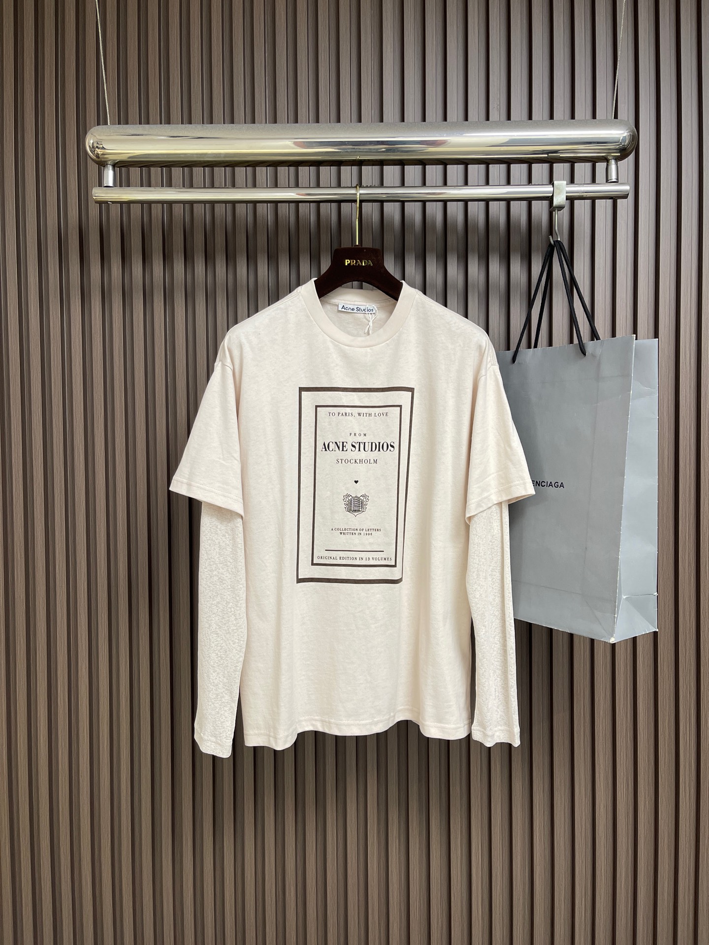 NO:842668,Acne Studios  There are two fake long-sleeved T-shirts in the collection of letters. The main fabric is 12-count fine cotton plain weave, 230gm; the ribbing uses 32-count double yarn, 350gm. 12-count is a coarse yarn count, which means that the yarn is thicker and has a lower twist. After being woven into plain weave, it will form an obvious slub feel or irregular texture. This kind of fabric  Abandoning the smoothness and delicacy of combed cotton, it deliberately retains a dry feel and slightly loose structure similar to a vintage distressed T-shirt. The weight of the fabric ensures that this rough texture will not collapse and can independently support a loose silhouette. The upper body will have a crisp paper feel and excellent breathability. The sleeves are made of polyester ribbing. Thorough use is used here  The heterogeneous splicing body is made of soft pure cotton, but the sleeves are made of functional chemical fiber. The polyester rib has natural elastic recovery and drape, which allows the sleeve shape to rebound quickly even after strenuous activities, without causing the bulging that is easy to occur in cotton cuffs. The seasonal pattern on the front chest uses a penetration printing process, through special additives and high-quality  Under high temperature and high pressure conditions, the dye molecules are completely dissolved and penetrated into the interior of the cotton fiber, and are covalently bonded with the fiber. For fabrics with uneven surface texture such as 12-count roving, penetration printing shows great advantages, and is evenly distributed along the fiber texture. The overall wiring is straight and delicate, the fabric is comfortable and soft, and the color is consistent without color difference.  It can be matched with the same style to create a fashionable look, and can be used in various occasions. Customized accessories, complete with three standards, same style for men and women!  Sizes XS-L19860909Acne Studios 信件合集假两件长袖T恤,主身面料选用的是12支精棉平纹,230gm；搭配罗纹采用了32支双纱,350gm.12支属于粗纱支,这意味着纱线较粗且捻度较低,织成平纹布后会形成明显的竹节感或不规则肌理.这种面料放弃了精梳棉的光滑细腻,刻意保留了一种类似复古做旧T恤的干爽手感和微疏松结构.面料克重确保了这种粗犷肌理不会垮塌,能独立支撑起宽松的廓形,上身会有一种挺括的纸张感,透气性极佳.衣袖采用了涤纶罗纹.这里运用了彻底的异质拼接衣身是柔软的纯棉,袖子却是功能性化纤.涤纶罗纹具有天然的弹性恢复能力和垂坠感,这使得袖型即使经过剧烈活动也能迅速回弹,不产生棉质袖口易出现的鼓包.前胸的当季图案采用了渗透印花工艺,通过特殊的助剂和高温高压条件,使染料分子完全溶解并渗入棉纤维的内部,与纤维发生共价键结合.对于12支粗纱这种表面肌理凹凸不平的面料,渗透印花展现了极大的优势,顺着纤维纹理均匀分布.整体走线平直细腻,面料舒适柔软,颜色一致无色差 能与同款搭配营造时尚造型,驾驭各种场合,定制辅料,三标齐全,男女同款！尺码XS-L XS码胸围120肩宽53衣长71.5 S码 胸围124肩宽54.5 衣长73.5 M码胸围128肩宽56 衣长75.5 L码 胸围132肩宽57.5 衣长77.5,,acne studios,dior,tees，t-shirt,,Men's clothing