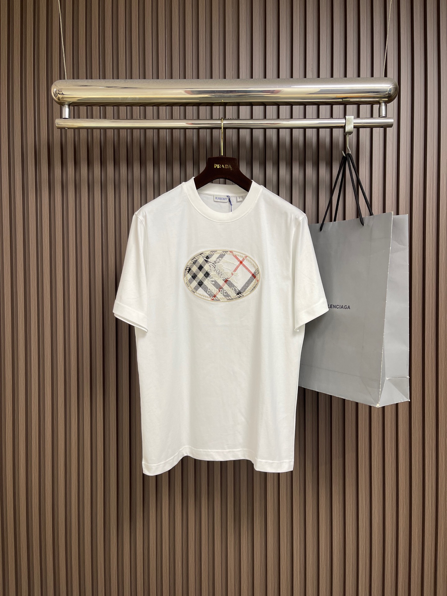 NO:842667,Burberry  The short-sleeved T-shirt with equestrian knight logo plaid print is made of imported high-count combed double-ply plain cotton fabric, which has been processed by pre-shrunk washing process. It feels soft and skin-friendly, has excellent breathable and moisture-absorbing properties, and is not easy to deform and pill after long-term wear. It has a soft drape texture, and the upper body silhouette is neat and not soft. The front of the body is printed with the brand's iconic oval plaid equestrian knight logo. It combines classic plaid elements with knight patterns and uses environmentally friendly reactive dyeing.  Printing technology, high color fastness, not easy to fall off and crack, clearly restore the brand's classic aesthetics; loose shoulder cut version, using ergonomic three-dimensional printing, the shoulder line naturally falls on the shoulders, modifying the head-to-shoulder ratio and body line, and has a high fit regardless of the body shape; the fabric has been specially treated with anti-wrinkle, making it easy to care for daily wear. It can not only create a casual and relaxed daily wear atmosphere, but also adapt to a variety of styles. Size XS-L  XS size bust 104 shoulder width 47 length 71.5 S size bust 108 shoulder width 48.5 length 73.5 M size bust 112 shoulder width 50 length 75.5 L size bust 116 shoulder width 51.5 length 77.5,,burberry,T-shirt,tees,t-shirt,19860909Burberry 马术骑士徽标格纹印花短袖T恤,采用进口高支精梳双股平纹棉面料,经过预缩水洗工艺处理,触感软糯亲肤,兼具优异的透气吸湿性能,久穿不易变形起球,自带柔和垂坠质感,上身廓形利落不软塌；衣身正面采用品牌标志性椭圆格纹马术骑士徽标印花,以经典格纹元素搭配骑士图案,采用环保活性染印技术,色彩牢固度高,不易脱落开裂,清晰还原品牌经典美学；宽松落肩剪裁版型,采用人体工学立体打版,肩线自然落于肩头,修饰头肩比与身形线条,不挑身材适配度高；面料经过特殊抗皱处理,日常穿着打理便捷,既能打造随性松弛的日常穿搭氛围,也能适配多种风格的穿搭场景.尺码XS-L XS码胸围104肩宽47衣长71.5 S码 胸围108肩宽48.5衣长73.5 M码胸围112 肩宽50衣长75.5 L码 胸围116 肩宽51.5 衣长77.5,,burberry,T-shirt,tees，t-shirt,,Men's clothing