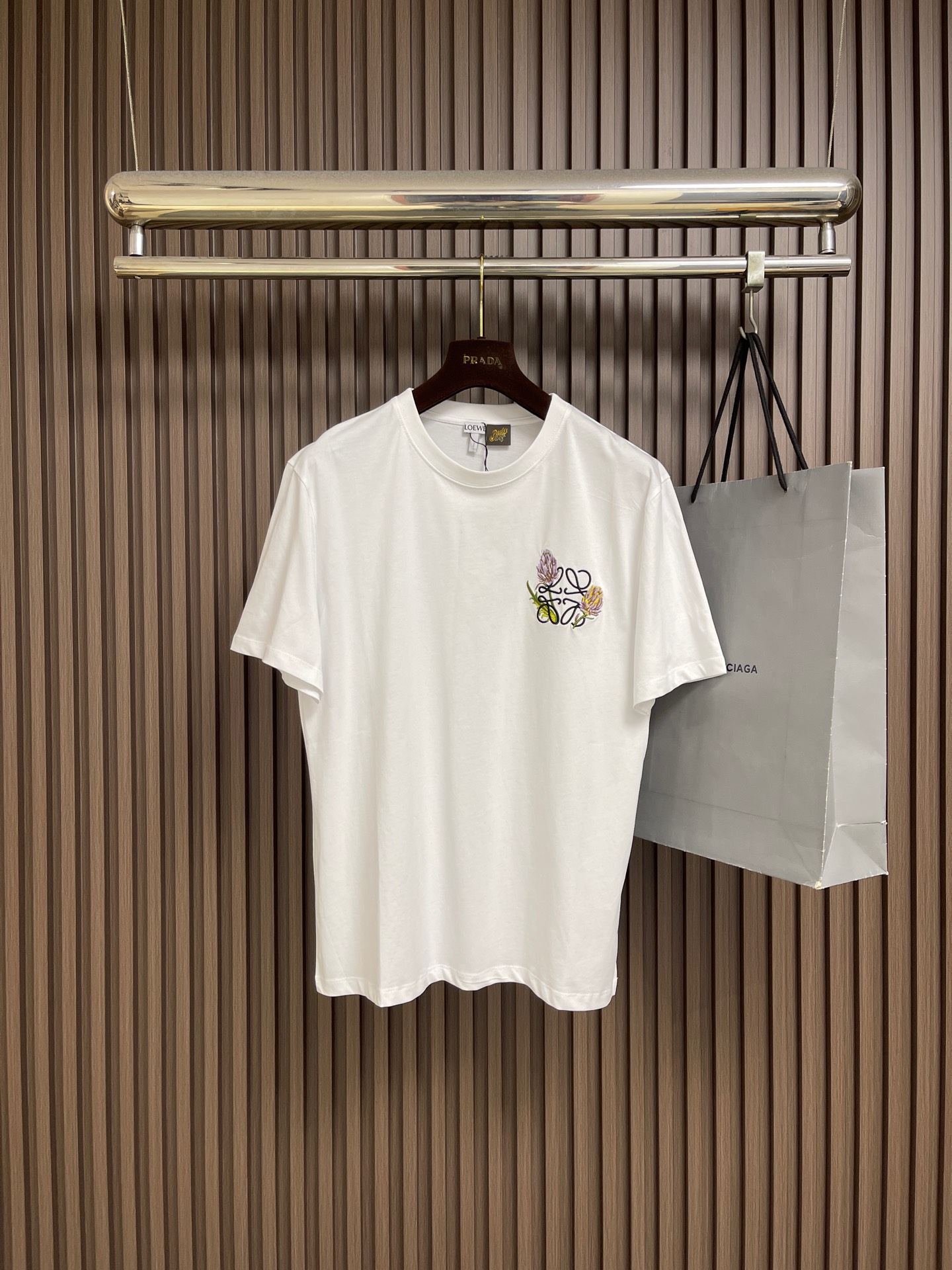 NO:839852,Loewe  Cotton Anagram flower embroidered T-shirt. This LOEWE short-sleeved T-shirt is made of high-count combed cotton fabric. The texture is soft and delicate, breathable and skin-friendly, and has good moisture absorption properties. It is smooth to the touch and not easy to deform. The classic round neck adopts reinforced hemming technology, the lines are smooth and fine, and the neckline is not easy to loose and deform after long-term wear. The brand flower embroidery on the left chest adopts precision three-dimensional embroidery technology, and the stitches are arranged evenly and tightly.  , the pattern outline is clear and full, the colors are rich, and the exquisite details are highlighted. The body adopts neat flat seam technology, the side seams are neatly routed, and the hem is solidly made. The overall tailoring is loose and smooth, taking into account both comfortable body feel and casual fit. It combines simple basic design with exquisite craftsmanship details, and has both daily wearability and high-end brand texture. The overall wiring is straight and delicate, the fabric is comfortable and soft, and the colors are consistent and without color difference.  It can be matched with the same style to create a fashionable look, and can be used in various occasions. Customized accessories, complete with three standards, same style for men and women!  Sizes XS-L19860909Loewe 棉质Anagram花朵刺绣T恤,本款LOEWE短袖T恤甄选高支精梳棉面料,质地柔软细腻,透气亲肤且具备良好吸湿性能,触感顺滑不易变形.经典圆领采用加固包边工艺,走线平整细密,领口久穿不易松垮变形；左胸品牌花卉刺绣采用精密立体绣制工艺,针脚排布均匀紧实,图案轮廓清晰饱满,色彩层次丰富,彰显精致细节.衣身采用利落平缝工艺,侧缝走线工整,下摆做工扎实,整体剪裁宽松流畅,兼顾舒适体感与随性版型,将简约基础款设计与精湛工艺细节融合,兼具日常实穿性与品牌高级质感.整体走线平直细腻,面料舒适柔软,颜色一致无色差 能与同款搭配营造时尚造型,驾驭各种场合,定制辅料,三标齐全,男女同款！尺码XS-L XS码胸围106肩宽48 衣长70 S码 胸围110 肩宽49.5 衣长72 M码胸围114 肩宽51衣长74 L码 胸围118 肩宽52.5衣长76,,loewe,T-shirt,tees，t-shirt,,Men's clothing