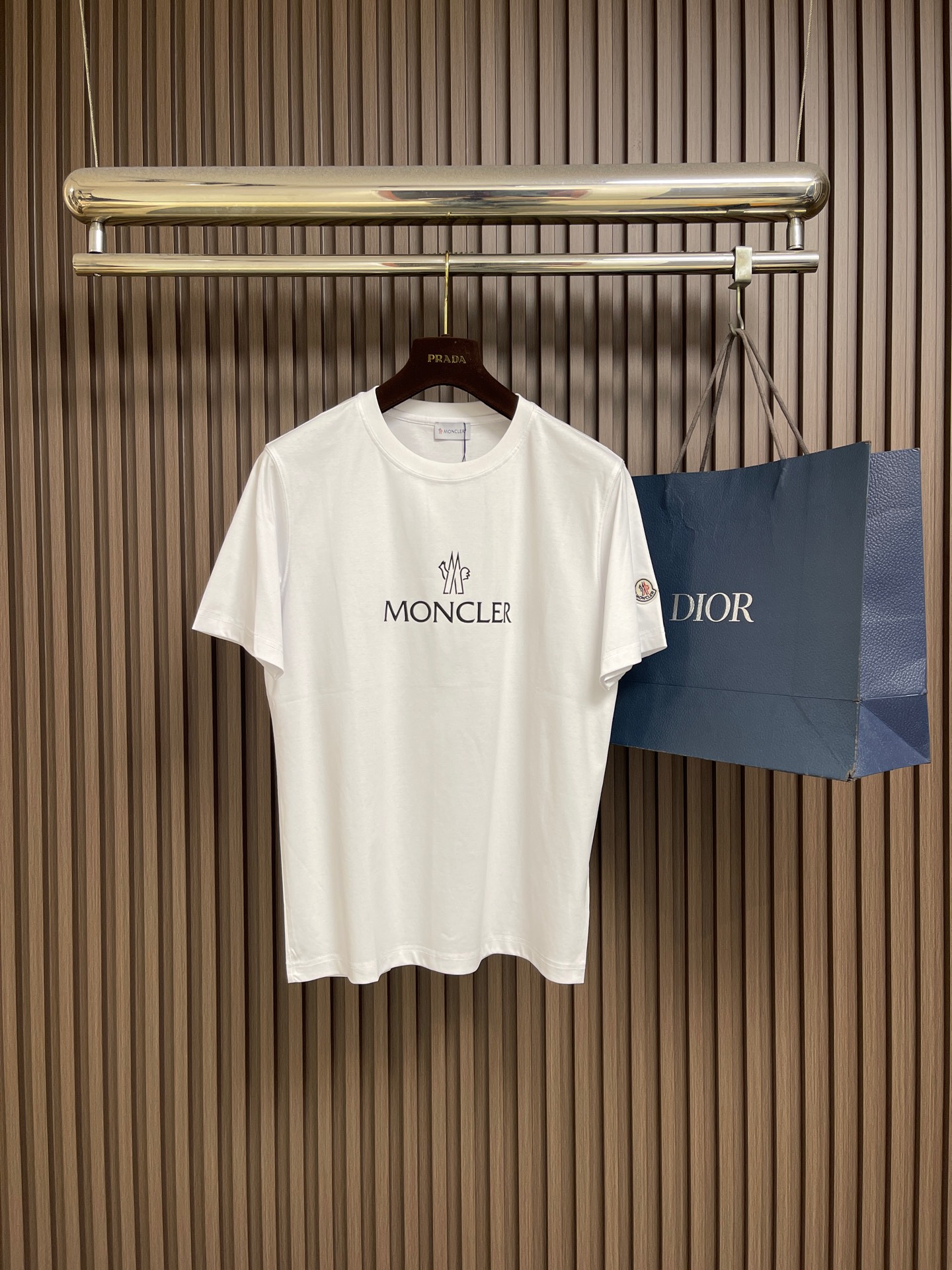 NO:839918,Moncler  Glue printed pattern round neck pullover short-sleeved T-shirt. This white short-sleeved shirt is made of high-count combed cotton fabric, treated with ammonia pre-shrinking and mercerization process. It feels smooth and skin-friendly, breathable and sweat-absorbent and has excellent wrinkle resistance. The color fastness reaches level 4 or above.  , not easy to yellow and deform after long-term washing. The neckline is made of high-elastic ribbing with three-needle hemming technology, which is not easy to loosen and curl after repeated wear; the side seams of the body are made of double-needle embedded clip technology, which ensures smooth and firm routing and reduces skin friction. Chest  The front brand logo adopts imported glue printing process, the pattern is clear and delicate, has strong adhesion and is not easy to crack and fall off; the cuffs and hem adopt flat seam sewing process, the stitching is fine and even, and there are no excess threads. The ready-made garments undergo multiple quality inspection processes such as stitching, ironing and decontamination. The version is loose and comfortable, suitable for daily commuting, leisure travel and other scenes, with both simple texture and practical wearability. The overall wiring is straight and delicate, the fabric is comfortable and soft, and the color is consistent without color difference.  It can be matched with the same style to create a fashionable look, and can be used in various occasions. Customized accessories, complete with three standards, same style for men and women!  Size M-3XL,,T-shirt,tees,t-shirt,19860909Moncler 胶浆印花图案圆领套头短袖T恤,这款白色短袖采用高支精梳棉面料,经氨预缩与丝光工艺处理,触感柔滑亲肤,透气吸汗且抗皱性优异,色牢度达4级以上,久洗不易发黄变形.领口采用高弹力罗纹搭配三本针包边工艺,反复穿着不易松弛卷边；衣身侧缝采用双针埋夹工艺,走线平整牢固,减少皮肤摩擦感.胸前品牌标识采用进口胶浆印刷工艺,图案清晰细腻、附着力强,不易开裂脱落；袖口与下摆采用平缝锁边工艺,针脚细密均匀,无多余线头.成衣经针、整烫、去污等多道质检工序,版型宽松舒适,适配日常通勤、休闲出游等多种场景,兼具简约质感与实穿性.整体走线平直细腻,面料舒适柔软,颜色一致无色差 能与同款搭配营造时尚造型,驾驭各种场合,定制辅料,三标齐全,男女同款！尺码M-3XL,,T-shirt,tees，t-shirt,,Men's clothing